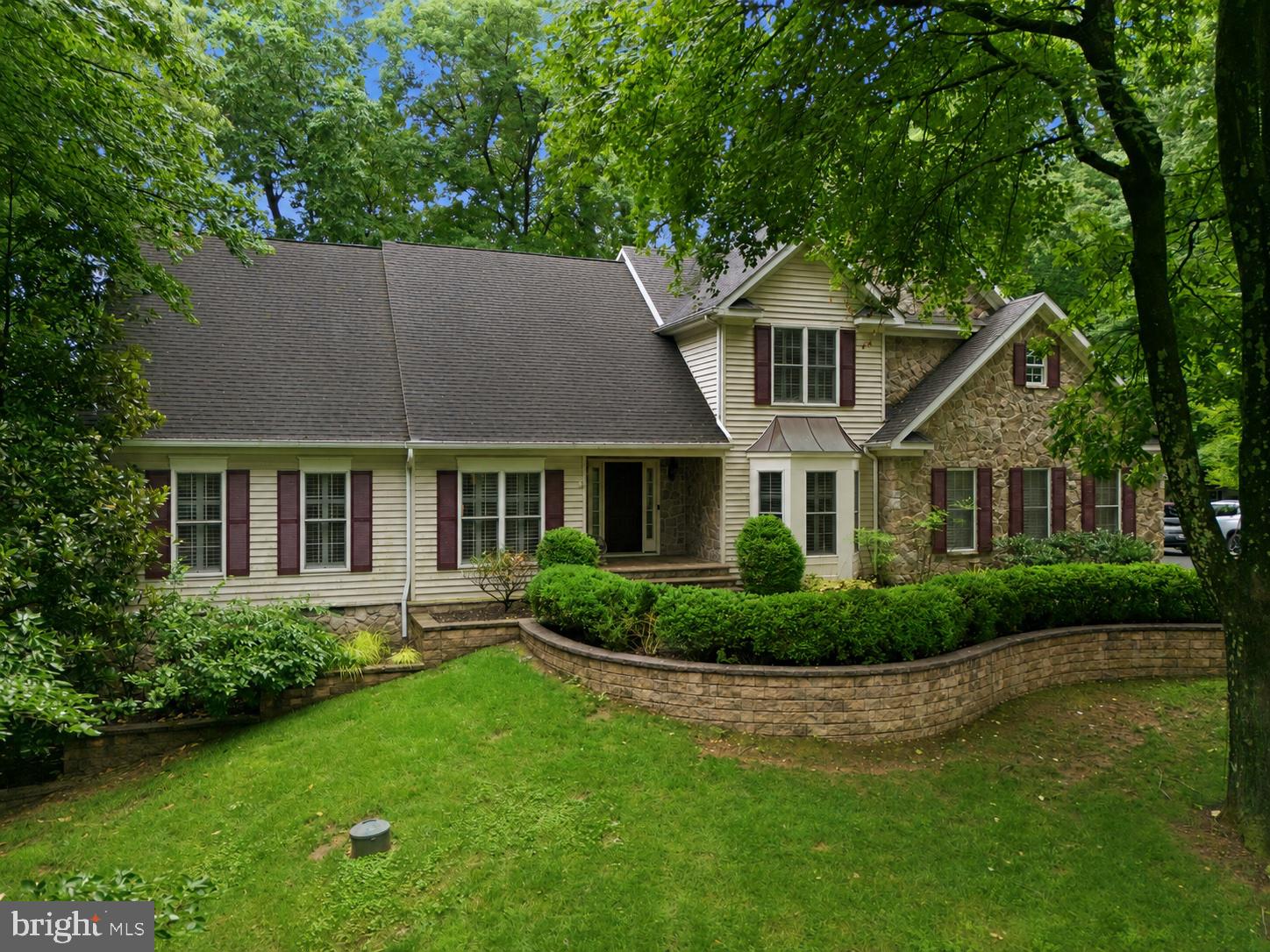 Nestled on a beautifully cared for one-acre lot surrounded by mature trees, this meticulously maintained home offers the perfect balance of privacy, space, and timeless design. With four bedrooms, three full baths, and one half bath, the thoughtfully designed floor plan is equally suited for everyday living and entertaining. 

The main level is anchored by a spacious primary suite, offering the ease of main-level living. Also on this level are a private home office with custom built-in bookshelves and desk, a formal dining room, and an expansive living room with soaring ceilings, abundant natural light, and seamless access to the rear deck.

The open-concept eat-in kitchen is designed for gathering, featuring granite countertops, stainless steel appliances, a large center island, abundant cabinetry, and generous prep space. Granite countertops continue throughout the home's bathrooms, creating a cohesive, high-end finish. A custom cast iron and hickory wood banister staircase connects all three levels, adding a distinctive architectural detail to the home's inviting design.

Upstairs, you'll find three generously sized bedrooms and a full bath. The finished walkout lower level offers exceptional flexibility with a comfortable recreation area, a striking glass-enclosed gym, and a large office or guest room with French doors opening to the lower patio. A full bath on this level adds convenience for guests or extended living. Two additional unfinished rooms provide abundant storage and future possibilities.

Outside, multiple outdoor living spaces, including an elevated deck and two patios, provide inviting spaces to relax or entertain while enjoying the home's peaceful, one-acre setting. An oversized attached two-car garage provides convenient access to the main level.

Ideally located in sought-after Woodbine, this exceptional home offers the tranquility of country living while remaining just minutes from commuter routes, shopping, dining, and everyday conveniences.