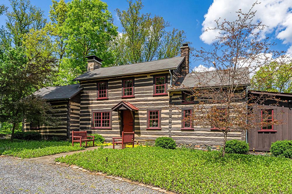 Set on a private ridge above the Shenandoah River with sweeping views of the Blue Ridge and Massanutten mountains, Shenandoah Overlook is a rare weekend retreat where three historic log cabins, a saltwater pool, and acres of landscaped grounds and woodland trails come together in remarkable seclusion.

Originally built in the 19th century on land that is now Shenandoah National Park, all three cabins were relocated here in the 20th century and have since been fully renovated in the 21st century for modern comfort while preserving their character — exposed beams, stone fireplaces, and white-washed log walls throughout.

Whether you’re hosting family and friends, hiking in the mountains, rafting on the river, or simply reading on the back porch as the light moves across the valley, Shenandoah Overlook was designed with family fun and relaxation in mind.   You can also very comfortably work remotely with Starlink internet and strong cell service.   Shenandoah Overlook is a turn-key property where nature and comfort meet — with everything in its place and nothing left to do.

Residences
The artfully restored main cabin features indoor entertaining spaces that blend seamlessly with outdoor living areas.   This comfortable home has plenty of space to unwind, enjoy the view, and even get a little work done in the library.  The other cabins exude charm and privacy as well, with all amenities.   Between all three cabins there are a total of 6 bedrooms and 3 bathrooms to allow for plenty of guests to enjoy the retreat.  Surrounding the cabins are other small log buildings to aid in storage and provide additional charm to the setting.  These include:

Fire Pit –  A metal lined stone faced fire pit near the two guest cabins.
Bank Barn – A log cabin with lots of storage space on two levels.  Ideal for small livestock or storing items safely in an enclosed space.
Cabin Shed – This small log cabin is a place for all pool equipment and lawn furniture tidily stored away.
Pool – An inviting gunite lined saltwater pool with flagstone coping just steps away from the house.  Automatic CoverSafe pool cover for ease of maintenance and safety.

The ultimate in privacy, Shenandoah Overlook is accessed by a long private right of way that opens up to a gentle ridge above the river.  Located along this ridge are the three cabins and outbuildings surrounded by lawns and landscaping and then woodlands beyond.   At strategic points in the forest, viewsheds have been opened up to provide stunning views of the river and the Blue Ridge and Massanutten mountains.  Expertly landscaped lawns and garden areas around each cabin provides outdoor living and playing space for your family, while providing four season garden interest as well.

More of the forested land could be cleared if desired, without compromising privacy.  There are three marked trails that meander through the woodlands.  A terrific feature is also a section of riverfront on the Shenandoah River, accessible via a hiking trail, for fishing, rafting, or just contemplating the beautiful setting.