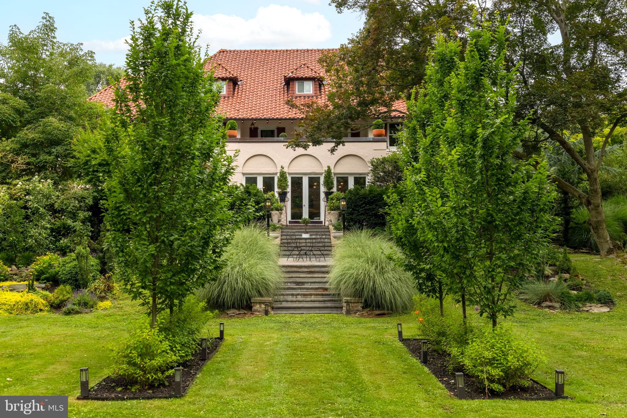 Featured on NBC's Today Show, HGTV, Philadelphia Magazine, and The Philadelphia Inquirer, this extraordinary 1915 estate residence combines thoughtful design, warmth, and functionality in a way that has garnered both local and national recognition.
 Evoking the charm of a Tuscan villa with its stucco exterior, terra cotta roof, enchanting gardens, and meandering stone pathways, the home offers a rare blend of historic character. One of its most remarkable qualities is the way it embraces its setting, with garden views visible from nearly every room and outdoor spaces thoughtfully integrated into daily living.
 An arched solid wood front door welcomes you into a grand foyer and introduces a home rich in architectural character. Five fireplaces, beautiful millwork, and thoughtfully preserved details create a sense of timeless elegance throughout. The formal living room flows seamlessly into the stunning Mercer tile sunroom, where French doors open to the patios and gardens beyond, connecting the home to the landscape.
 One of the home's most distinctive spaces is the library, a dramatic room that currently serves as a whiskey lounge. Featuring extensive custom woodwork, dark designer finishes, a fireplace, built-in bookcases, and French doors opening to the grounds, this unforgettable space offers warmth, character, and an inviting place to gather.
 The formal dining room, featured as part of the home's nationally recognized renovation, opens directly to the gardens and outdoor living spaces. At the heart of the home is a beautifully designed gourmet kitchen created for gathering, entertaining, and everyday living. A spacious butler's pantry and mudroom provide both convenience and functionality while maintaining exceptional practicality.
 The second floor is home to a luxurious primary suite retreat. The suite includes a spa-inspired bath and an extraordinary custom dressing room with a center island, washer/dryer, and access to one of the home's most remarkable features—a fully copper-lined balcony overlooking the gardens and grounds. Private and unlike anything typically found in the area, this exceptional outdoor retreat offers a peaceful place to begin or end the day and a front-row seat to the moon rising over the property. Additional bedrooms and a hall bath complete this level.
The third floor offers additional bedrooms, a full bath, generous storage, and the Philadelphia Magazine featured guest room.
The finished lower level is designed for recreation, fitness, entertaining, and everyday convenience, featuring a game room, exercise room, utility and storage areas, and a refreshment center with butcher block countertops, cabinetry, a laundry center, under-counter freezer, and two-drawer refrigerator.
The grounds are every bit as special as the home itself. Meandering patios, stone steps, winding garden paths, mature plantings, a rose garden, herb garden, a lane of columnar apple trees and espalier, potting shed, extensive landscape lighting, irrigation system, and multiple secluded sitting areas create a series of outdoor rooms designed for both quiet reflection and entertaining. A hammock retreat, honeysuckle-covered trellis, and thoughtfully placed gathering spaces invite exploration throughout the property. The fully fenced grounds enhance the estate-like setting.
 A piece of Jenkintown history, this home was featured in the original circa-1928 Jenkintown Manor development brochure. Remarkably, the stone column pictured in the brochure remains standing on the property today.
 The detached two-car garage includes two second-floor bonus rooms offering exceptional flexibility for a studio, workshop, or additional storage.
 With six bedrooms, three full baths, one half bath, nationally recognized design, and remarkable architectural character, this is a rare opportunity to own one of Abington Township's most distinctive homes—where history, craftsmanship, gardens, and thoughtful design create unforgettable living.