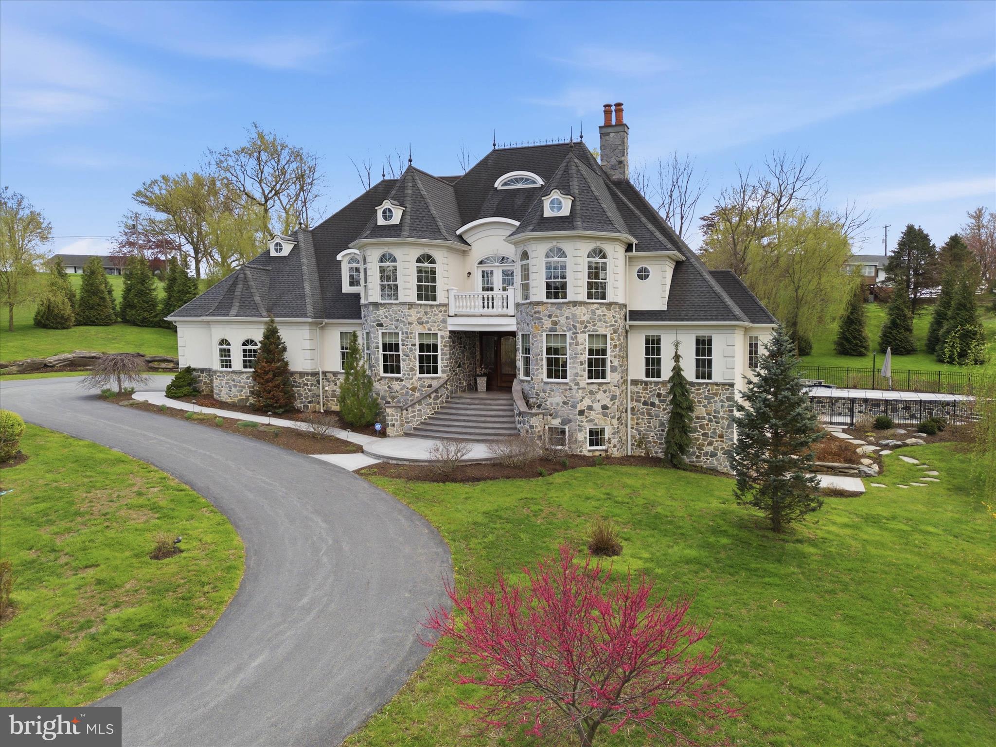 Set on over two acres in the quiet setting of Farview Farm Estate, this custom-built home offers a level of space, craftsmanship, and privacy that’s hard to come by in Lancaster County.
From the moment you walk in, the scale and detail stand out. The two-story great room anchors the home with a floor-to-ceiling stone fireplace, custom built-ins, and natural light pouring in through oversized windows. It’s open, inviting, and designed to feel just as comfortable on a quiet evening as it does while entertaining a home full of guests.
The kitchen was designed for someone who truly enjoys cooking and gathering. With an expansive island, copper sink, walk-in pantry, and clean, high-end finishes throughout, it flows seamlessly into both a relaxed sitting area and a more formal dining space. The dining room is framed by coffered ceilings, detailed millwork, and a wet bar with wine storage, creating an ideal setup for both intimate dinners and larger gatherings.
The owner’s suite is privately tucked away and includes its own fireplace, tray ceiling, direct access to the rear patio, a spacious walk-in closet, and an en-suite with radiant heated floors, a large glass-enclosed shower, and a clawfoot tub. A second suite on the opposite side of the home offers flexibility for guests or multigenerational living. Just inside from the three-car garage, a thoughtfully designed mudroom includes a dedicated pet washing station or additional clean-up space.
Upstairs, you’ll find three more bedrooms with a mix of private and shared bath layouts. A bonus room provides even more flexibility, whether it’s used as a second office, gym, or media space. From the upstairs sitting area, French doors lead out to a balcony overlooking the property, a quiet spot to start or end the day.
The lower level adds over 2,000 square feet of finished space designed with entertaining in mind, complete with a custom bar, media area, full bath, and a large custom-designed wine storage area that adds both character and function.
Out back, the setting opens up even further. A newer heated saltwater pool creates a true backyard retreat, with a shallow lounging area ideal for relaxing or sunbathing, along with a deeper section designed for swimming and even pool volleyball. The surrounding patio offers both covered and open-air spaces, a fireplace, and built-in seating, creating a natural extension of the home for hosting or unwinding. Mature landscaping and a partially wooded backdrop enhance the sense of privacy, with frequent visits from local wildlife.
Built by RL Hershey Custom Homes, the property carries quality throughout, from the hardwood flooring and natural stone finishes to the integrated smart home system managing lighting, audio, climate, and more. Even the roof reflects the level of craftsmanship, featuring hand-hammered individual shingles designed with a 50-year lifespan.
All of this, just minutes from downtown Lancaster, Millersville University, and local favorites like Cherry Hill Orchards.
If you’ve been waiting for a home that offers both presence and practicality, along with spaces designed to bring people together, this is one worth experiencing in person.