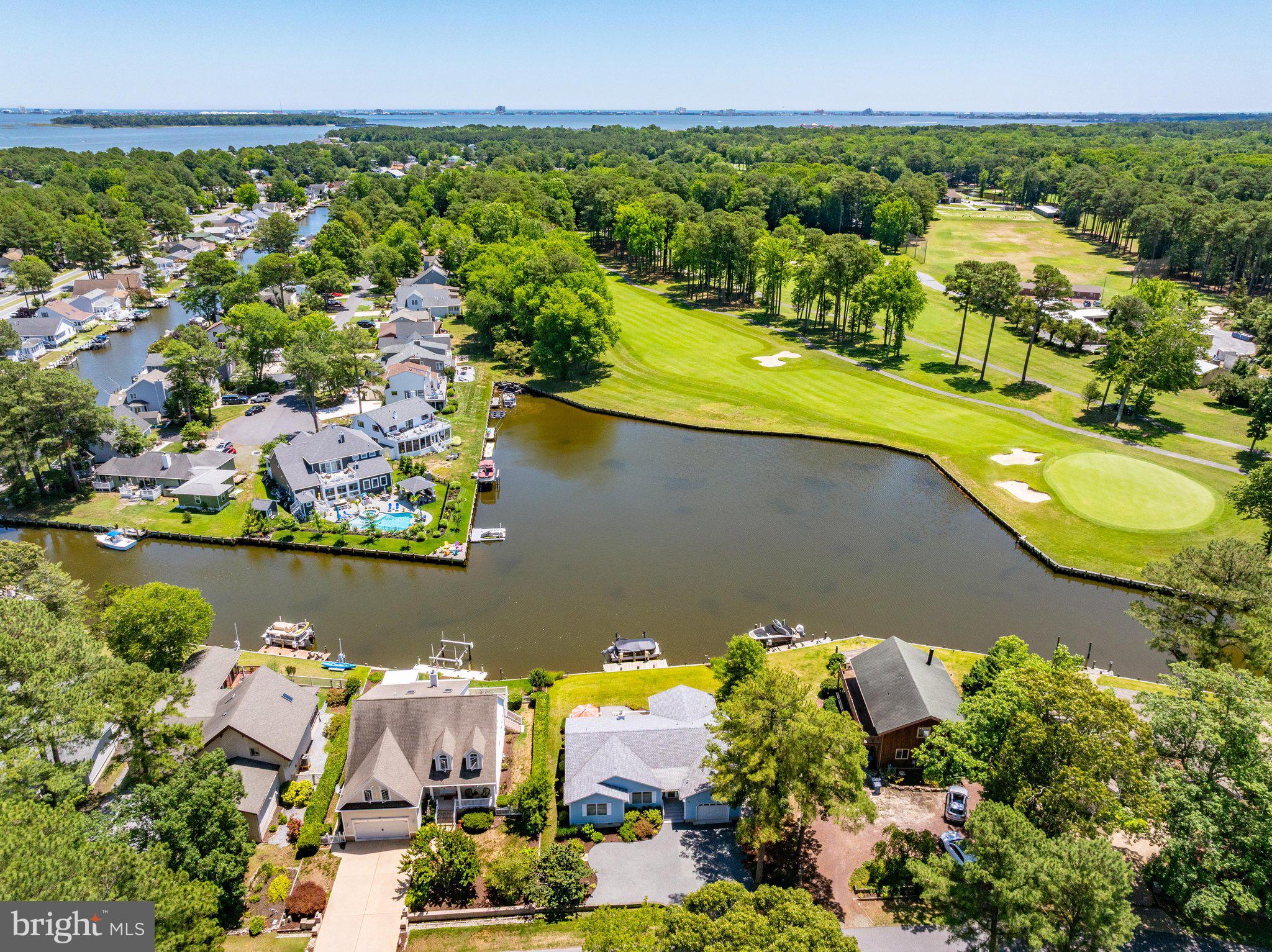 Don’t Miss your Chance to enjoy the BEST panoramic Canal and Golf Course Views in Ocean Pines!!! The extra large, rear deck and fully screened porch offer unobstructed scenic views. There are roll-down sunshades on the screened porch, and beautifully landscaped grounds with irrigation, paver walkways, and a private boat dock with lift.  Brand new stainless steel appliances, single  basin sink, quartz countertops, and Fabuwood  cabinets highlight the welcoming kitchen. The living room features a beautiful corner-set gas fireplace and built-in display storage shelving. Real bamboo hardwood flooring  accents all living areas and bedrooms, while porcelain tile is found in the foyer, kitchen, and baths.  All three bathrooms have been tastefully updated, while all bedroom closets have built-in organizers and lighting.  In  the garage with extra-tall ceiling height, you will find lots of cabinet storage, work surface, and a utility sink. A brand new dehumidifier was recently  installed in the crawlspace, a whole house carbon water filtration  system is included, and the 2 x 6 wall studs offer strong construction and deeper window sills throughout.   Six vehicles will fit nicely in the thoughtfully designed driveway.  There are so many more upgrades to discover in this home, located on a wide street in a quiet and lovely neighborhood!!