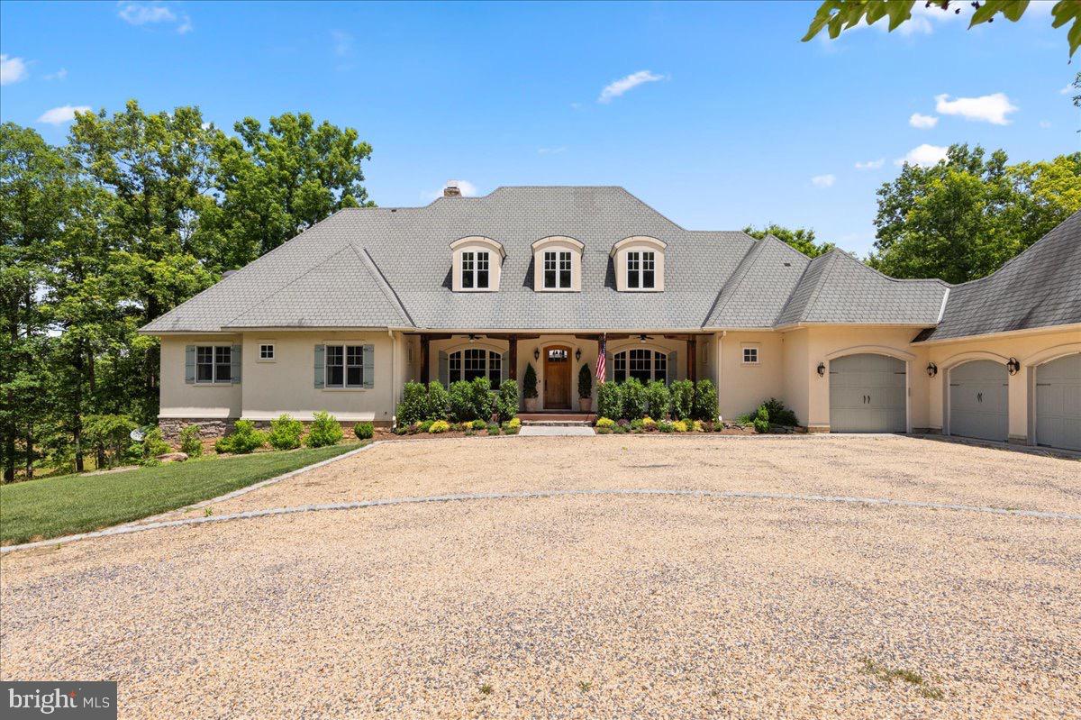 Discover unparalleled elegance in this French Country estate, masterfully crafted by Amish builders on over 15 acres of pristine, Fauquier countryside.
Nestled deep in a serene, wooded haven, this stunning 5 bedroom/4.5 bath home offers the perfect blend of timeless European charm and exceptional American craftsmanship. From the moment you arrive via the winding 1/2 mile driveway, the peaceful tranquility envelops you — with rolling meadows, a private pond, and dense forest providing complete privacy and a profound sense of escape.
The exterior showcases classic French Country architecture with graceful dormer windows, stone accents, a stately gray shingle roof, and a welcoming facade framed by mature trees and lush landscaping. Multiple garages and expansive outdoor spaces complete the picture of refined country living.
Inside, the home impresses with soaring cathedral ceilings, dramatic exposed timber beams, and intricate Amish-built woodwork throughout. A magnificent two-story stone fireplace serves as the heart of the grand great room, bathed in natural light from walls of oversized windows that frame breathtaking forest views. Teak hardwood floors, custom millwork, a gourmet kitchen, formal dining room with crystal chandelier, and luxurious primary suite with spa-like bath all reflect uncompromising quality and elegant taste. Below, a separate one bedroom apartment offers, flexibility for live-in assistance, second generation or additional income.  Upgraded mechanical offers comfortable living. 
Step outside to multiple decks and a spacious stone patio — ideal for entertaining or simply savoring the quiet beauty of your private sanctuary. Whether enjoying morning coffee overlooking the pond or hosting family gatherings under the stars, this property delivers peace, privacy, and timeless sophistication.
A rare opportunity to own a true legacy home in one of the most tranquil settings imaginable close to Orlean in the Town of Marshall. Perfect for those seeking elegance, quality, and a deep connection to nature just one hour to the Nation’s Capital.