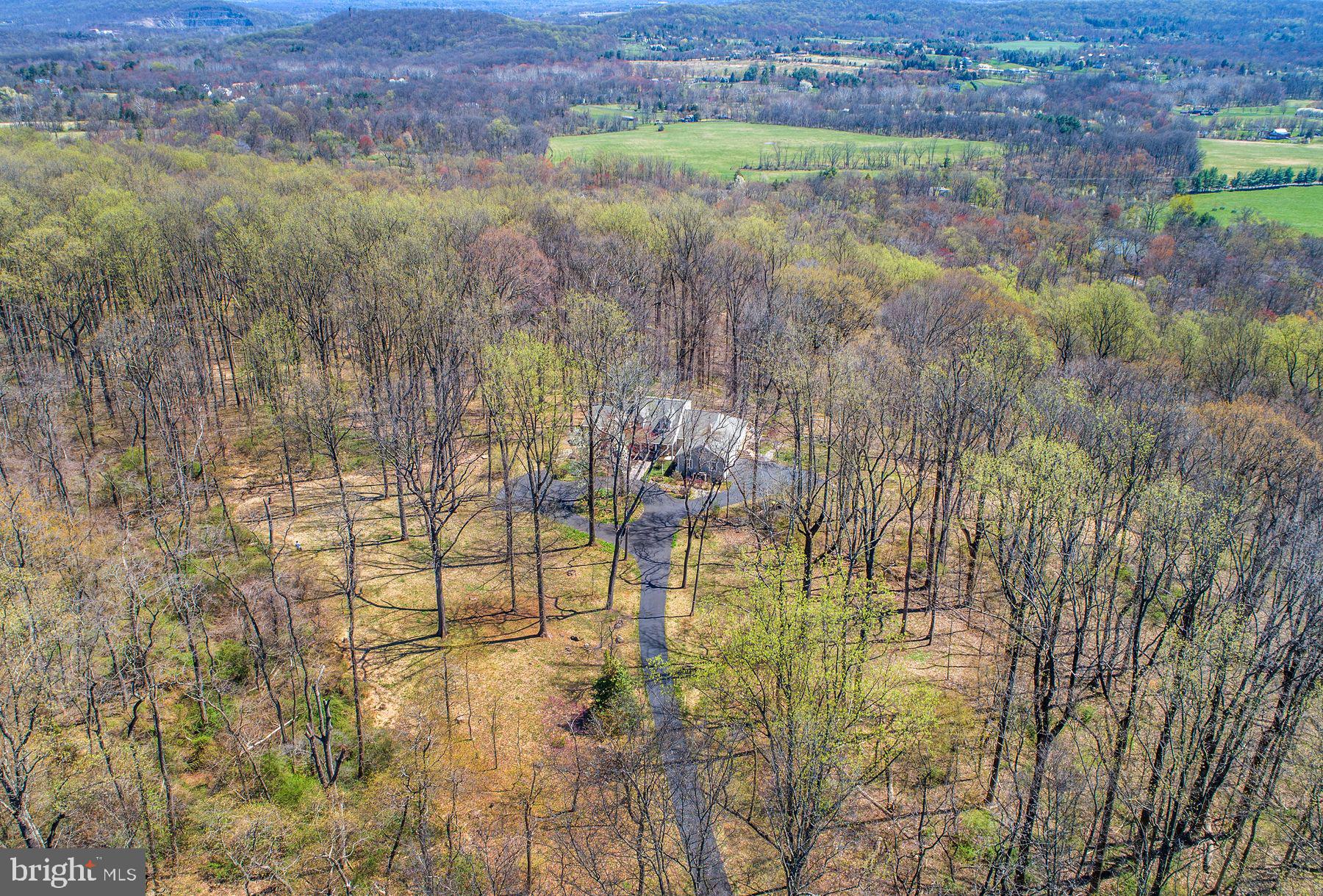 Showing begin on Sunday, May 31st at the Public Open house from 12:00-3:00. This custom Cape enjoys serene privacy on 11 acres at the end of a long serpentine driveway and is perched high on the south side of Solebury Mountain. The lovely home rests in a clearing & is surrounded by tall matures trees. It overlooks seasonal views across Solebury, Upper Makefield farmland & hills in the distance. Expansive windows create walls of glass bringing the outside in & provide glorious light as you look onto a forested hillside. The floor plan is open, versatile, relaxing & comfortable. The two-story entrance foyer is complemented by custom tile flooring with parquet accents. The living room with large field-stone mantled fireplace seamlessly brings you to the adjacent dining area with cathedral ceiling & eye-catching transom window. A wet bar is conveniently located between the living room & dining area for entertainment. An adjacent door takes you to a large sweeping Ipe wood deck. It offers the perfect place for intimate seasonal dining and relaxation with family & friends. The bright & sunny custom center-island kitchen with generous high-hat lighting, abundant cherry cabinetry, granite counters, stainless appliances and ceramic floor offers great space for planning meals. There is additional built-in shelving and a walk-in pantry too! An informal flex space is dovetailed between the kitchen and dining area. It provides flexibility for a media room, den or a casual spot for breakfast   dinner. Track lighting is focused on custom shelving for your art & collectibles. A real bonus is the first-floor primary bedroom suite with 2 walk-in closets. Its custom bath features double vanity, soaking tub & oversized shower with seamless door. There is an additional full bath on the first floor with shower & granite top vanity.  Staircase from the foyer takes you to the second floor and 2 additional bedrooms, each with walk-in closets and a full hall bath with tub/shower & dormer window. The lower walk-out level of this appealing home provides a myriad of uses with a full bath + storage. Sliding doors run the length of the rear wall. Completing the amenities are an attached 3 car garage & propane powered generator providing the comfort of backup power. Located in an exceptionally beautiful area of preserved land, fine homes & a few minutes to restaurants & shops of New-Hope   Lambertville.