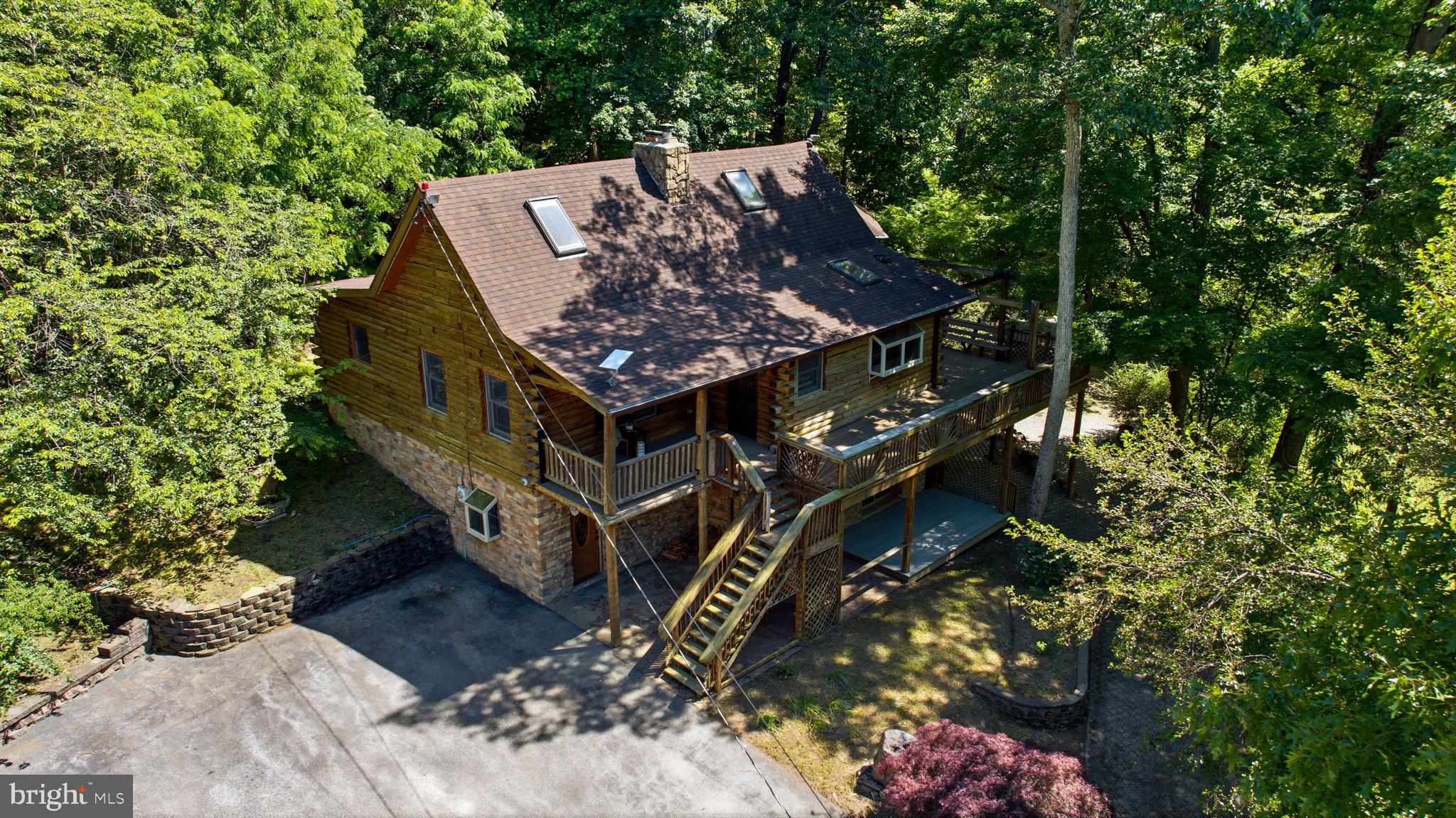 Tucked away on 12.5 wooded acres just moments from the Appalachian Trail, this one-of-a-kind log cabin offers the kind of privacy, character, and natural beauty that is hard to find. Surrounded by mature trees and peaceful mountain scenery, the home blends rustic charm with thoughtful custom details throughout.

Inside, a striking stone accent wall, wood stove, and unique antique freezer-door storage create an unforgettable first impression. The lower level features a spacious primary bedroom with custom built-in closets, along with a full bath and oversized soaking tub. On the main level, the kitchen is both beautiful and functional with soapstone countertops, a farmhouse sink, and a commercial gas range, all opening into a warm and inviting great room designed for gathering.

Two additional bedrooms offer flexibility, perfect for guests, an office, or creative space. A second full bathroom features a large walk-in shower with custom jets. Upstairs, a charming loft overlooks the great room and offers the perfect spot for reading, relaxing, or additional living space.

Outdoor living is just as special, with a wraparound Trex porch leading to a screened porch where you can enjoy the quiet surroundings in every season. The large detached garage includes a working motorcycle lift and second-floor storage, while the expansive patio space creates a true outdoor haven with plenty of room to relax, entertain, dine under the trees, or simply take in the peace and privacy of the property.

With room to roam, space to create, and nature right outside your door, this secluded mountain retreat offers a rare opportunity to enjoy peaceful living just steps from adventure.