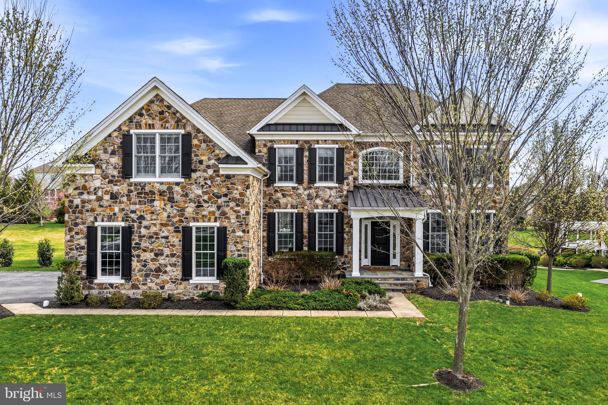 Built just 10 years ago, this stately stone Colonial in the highly desirable Liseter community offers a blend of timeless elegance, modern comfort, and exceptional convenience. Ideally positioned within the neighborhood, the home enjoys picturesque front-to-back green views and easy walkability to the community pavilion, park, fitness center, pool, and tennis courts.  A grand two-story foyer welcomes you, highlighted by a sweeping staircase and flanked by formal living and dining rooms. The living room features refined wainscoting, crown molding, and a glass door that connects effortlessly to the heart of the home. The dining room mirrors these elegant finishes, enhanced by recessed lighting and expansive windows capturing stunning sunset views.  At the center of the home, the great room offers rich hardwood flooring, a cozy gas fireplace, and an open flow into the beautifully appointed kitchen. Designed for both everyday living and entertaining, the kitchen features a large island with seating, stainless steel appliances, gray granite countertops, and under-cabinet lighting. Just beyond, a vaulted sunroom impresses with a second fireplace, walls of windows, and French doors leading to the rear deck and flat backyard.  Additional main-level highlights include a spacious pantry, a mudroom with laundry leading to the attached side-entry three-car garage, and a private office that can easily serve as a first-floor guest bedroom with access to a full bath.  Upstairs, a wide hallway leads to four generously sized bedrooms and a versatile bonus area—ideal for a homework station, lounge, or play space overlooking the backyard. The luxurious primary suite serves as a true retreat, featuring a sitting area, hardwood floors, three walk-in closets, a vanity area, and a spa-like bath with dual vanities, soaking tub, glass-enclosed shower, and private water closet. One secondary bedroom offers an en suite bath, while the remaining two share a well-appointed hall bathroom.  The fully finished walk-out lower level was completed in 2019 and significantly expands the living space, offering a fifth bedroom or nanny suite complete with a kitchenette and full bath. This level provides approximately 2,000 additional square feet of finished space—perfect for recreation, entertaining, or extended-stay living—bringing the home’s total living area to over 8,000 square feet.   To complete this Bryn Mawr Duke Model/Style home is a full house generator this alleviates any worry of missing power any day of the year. Located in the sought-after Liseter community, residents enjoy resort-style amenities including an infinity pool, clubhouse, fitness center, tennis courts, walking trails, and parks. Don’t miss the opportunity to own this exceptional home—schedule your private tour today.
