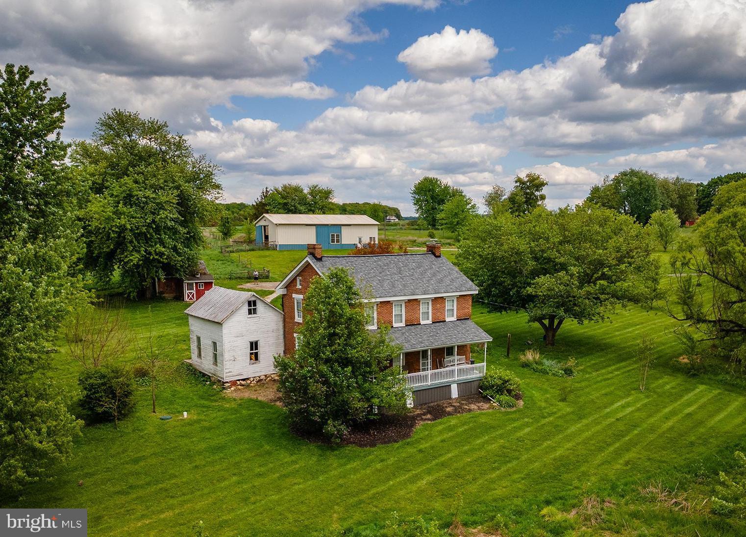 OPEN HOUSE SATURDAY (6/6) FROM 1-3PM!! Your dream of a functional farmette on over 10 acres with classic brick farmhouse in Carroll County can be realized at 2100 Blacks Schoolhouse Road.. Warm, inviting, and with all main systems and roof completely recently updated, you'll enjoy all modern conveniences combined with the charm of yesteryear - but without the worry! The wonderful back porch takes you inside the main level, which features hardwood floors, newer appliances, an open country-style eat-in kitchen with wood stove, and plenty of room for a large table. A separate formal dining room provides flexibility for a first-floor office or playroom if preferred, while the adjacent living room is just off the kitchen. A half bath with washer/dryer and plumbing in place for a shower complete the first floor. With laundry also able to be relocated upstairs, the space provides plenty of opportunity for a second full bath or keep as-is! Upstairs,find three spacious bedrooms with wonderful natural light, a very large updated full bath with tub/shower combo, and walk-up access to the attic for additional storage. The house is painted in a neutral palette throughout and is just one of those cozy, inviting spaces you can't help but feel "at home" in. There is also a large summer kitchen attached under the porch that would serve wonderfully continued to be used as storage or renovated into additional living space - a primary suite, family room, office, or even attached garage! Outside, find multiple fenced pastures and a large, center-aisle barn with space for at least 4 stalls, equipment parking, water and electric, ready for your animals, homesteading accessories, parking - whatever you need! The topography is gently rolling with plenty of flat, usable acreage and the pasture is plentiful! Additional outbuildings include a shed and chicken coop, all in a pastoral setting with room to expand your vision - gardens, animals, equipment, future improvements, or simply open space to enjoy. Whether you dream of bringing horses home, starting a hobby farm, or settling into a slower lifestyle with room to roam, this 10-acre farmette is the perfect setting to plan your future chapters. Quiet, functional, and full of possibility - come explore the potential!