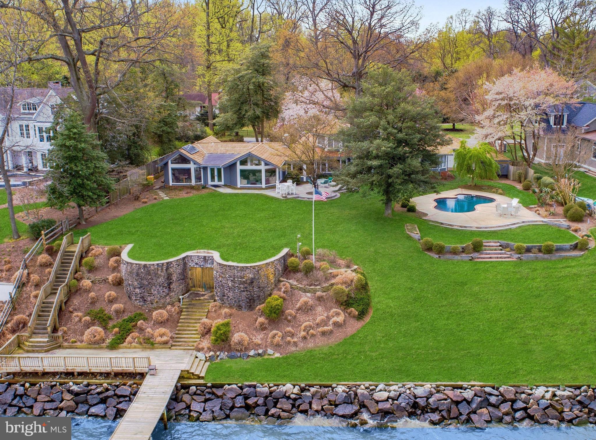 Extraordinary Chesapeake Bay waterfront is priced for immediate sale and showcases distinctive features and limitless potential / Red cedar cathedral ceilings with exposed beams, custom pyramid skylights and walls of glass with vast Bay views extend the full length of the home / Hardwood floors extend throughout most areas / 2004-2006 renovation included a 2 car garage addition, existing space was reconfigured to create a superb Owners Suite with Luxury bath, and the kitchen was renovated and expanded / Chefs Kitchen is outfitted with a 12 ft granite island, extensive cabinetry, twin Sub Zs, Miele cook top and double oven / Owners Bedroom highlights built-in bookcases, exposed beam ceilings, panoramic Bay views and the Luxury Bath offers generous granite counter space, jet tub, oversize double-head shower and vaulted ceiling with skylight / Upper level octagonal suite features a fireplace, built-in bookcases and sweeping Bay views / Perimeter landscaping and hardscaping and waterfront decks and swimming pool maximize this sought-after location / Sea wall and rip rap completed 2004-2005 / private pier with lift extends from the 41 X 9 waterfront deck / Take note of the tunnel exit within the stone retaining walls, constructed in the 1940s, which extends 70 ft from the basement to the waterfront! It was constructed with a concrete foundation and walls forming a 9 X 9 opening and is ideal for deck furniture and boating supplies storage / Tax records are incorrect: this is a double lot with a footprint that consists of over 5,000 sq ft including the garage, and incorporates approx. 4,500 sq ft of living space on the main level plus an upper level bedroom suite / Most photos have been virtually staged