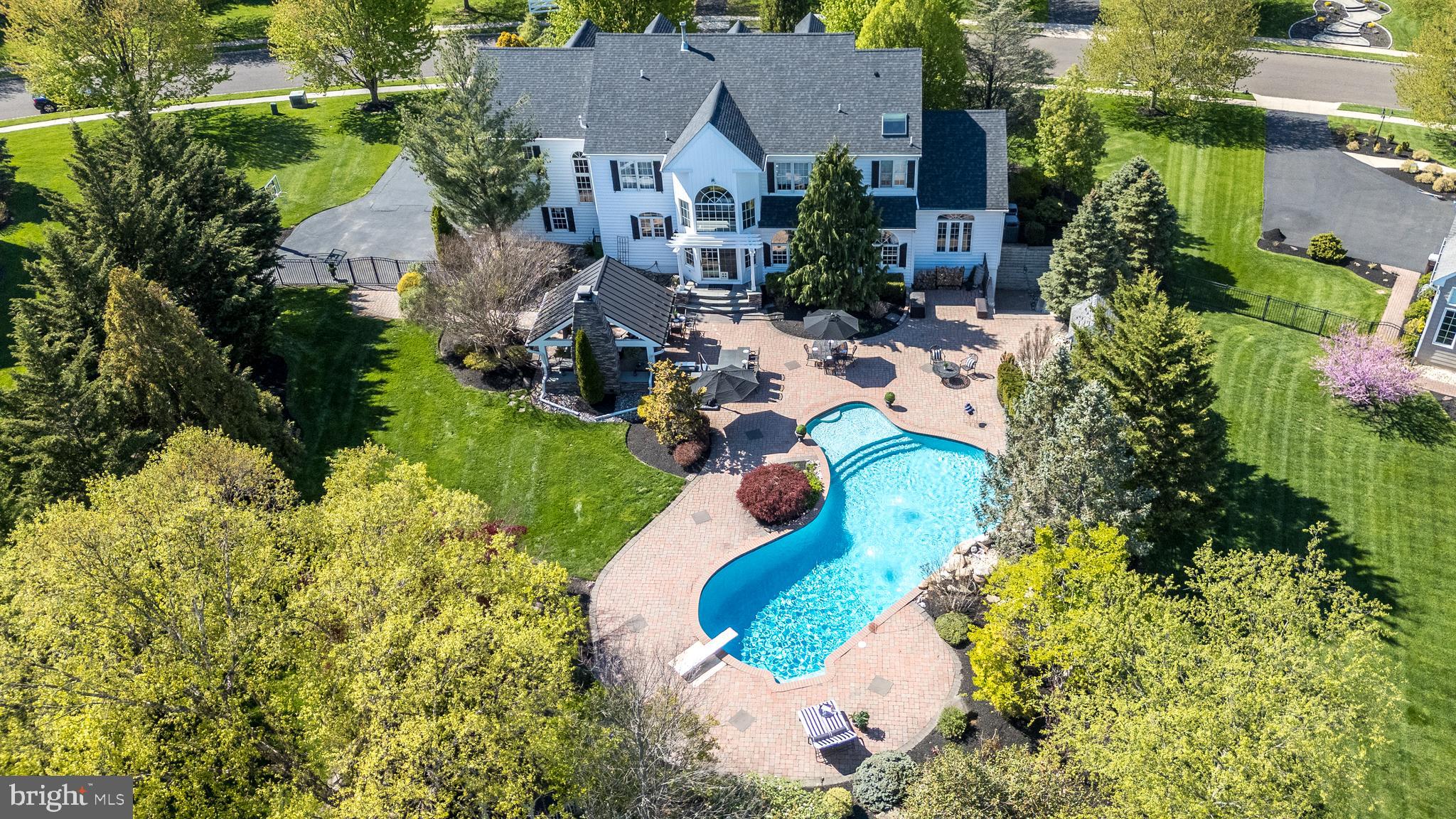 Rarely does a home of this caliber become available in such an intimate and highly sought-after community. Welcome to 2209 Denbeigh Drive, an extraordinary estate nestled on nearly an acre in the prestigious Estates at Warwick Lea, where timeless elegance, exceptional craftsmanship, and resort-style living come together to create an unparalleled lifestyle. Perfectly positioned on a premium lot backing to preserved open space and mature trees, this remarkable property offers a rare blend of privacy, tranquility, and breathtaking outdoor beauty.

This magnificent residence offers 5 spacious bedrooms, 4 full baths, 1 half bath, a finished lower level, and an extraordinary backyard retreat designed for both grand entertaining and everyday enjoyment. The outdoor oasis is truly breathtaking, featuring a heated saltwater pool, expansive patio, charming gazebo, and an outdoor living room anchored by a stunning stone fireplace. Beautifully manicured grounds and picturesque views of the surrounding open space create a setting reminiscent of a private luxury resort.

From the moment you arrive, the home's stately presence is undeniable. A graceful curved walkway leads to the impressive brick façade, highlighted by a new double front entry door and lush, professionally designed landscaping that creates a memorable first impression.

Step inside to discover a grand two-story foyer adorned with gleaming marble flooring and crowned by a dazzling crystal chandelier that casts a warm, elegant glow throughout the entrance. Every room has been thoughtfully designed to balance sophistication with comfort and functionality.

The main level offers an exceptional collection of living spaces, including a private study, elegant formal living and dining rooms, an expansive family room, a spectacular conservatory, and a dramatic two-story breakfast room filled with natural light and scenic views of the grounds. At the heart of the home is the beautifully updated chef's kitchen, featuring custom cabinetry, premium finishes, thoughtfully designed built-ins, and abundant space for both entertaining and everyday living.

Adding to the home's functionality is the recently expanded laundry and mudroom, complete with its own private entrance and newly constructed covered porch.

The second floor is home to five generously sized bedrooms, including an extraordinary primary suite that serves as a private sanctuary. This luxurious retreat features a spacious sitting room, a custom walk-in closet, and an expansive spa-inspired bath. One secondary bedroom offers a private en-suite bath, while the remaining bedrooms are served by an additional full bath, providing ample space and comfort for family and guests alike.

The finished lower level is equally impressive, offering a large recreation room, fitness area, full bath, and direct access to the backyard retreat—creating the perfect space for entertaining, exercise, hobbies, or extended guest accommodations.

Significant recent improvements include:

• Newer Roof
• Newer Siding
• Newer Shutters
• New Double Front Entry Door
• Updated Chef's Kitchen
• Expanded Mudroom & Laundry Room
• Newer Covered Porch
• Newer Dual-Zone HVAC Systems
• Newer Water Heater

Beyond the property itself, the location is exceptional. Residents enjoy the award-winning Central Bucks School District, nearby parks and walking trails, and convenient access to the charming shops, restaurants, and cultural attractions of Doylestown Borough. Commuters will appreciate the ease of travel to New Jersey, Philadelphia, New York City, Routes 202 and 611, I-95, and the Pennsylvania Turnpike.
Properties offering this level of privacy, outdoor living, and refined elegance rarely come to market and are even more rarely found in such a convenient Bucks County location.
