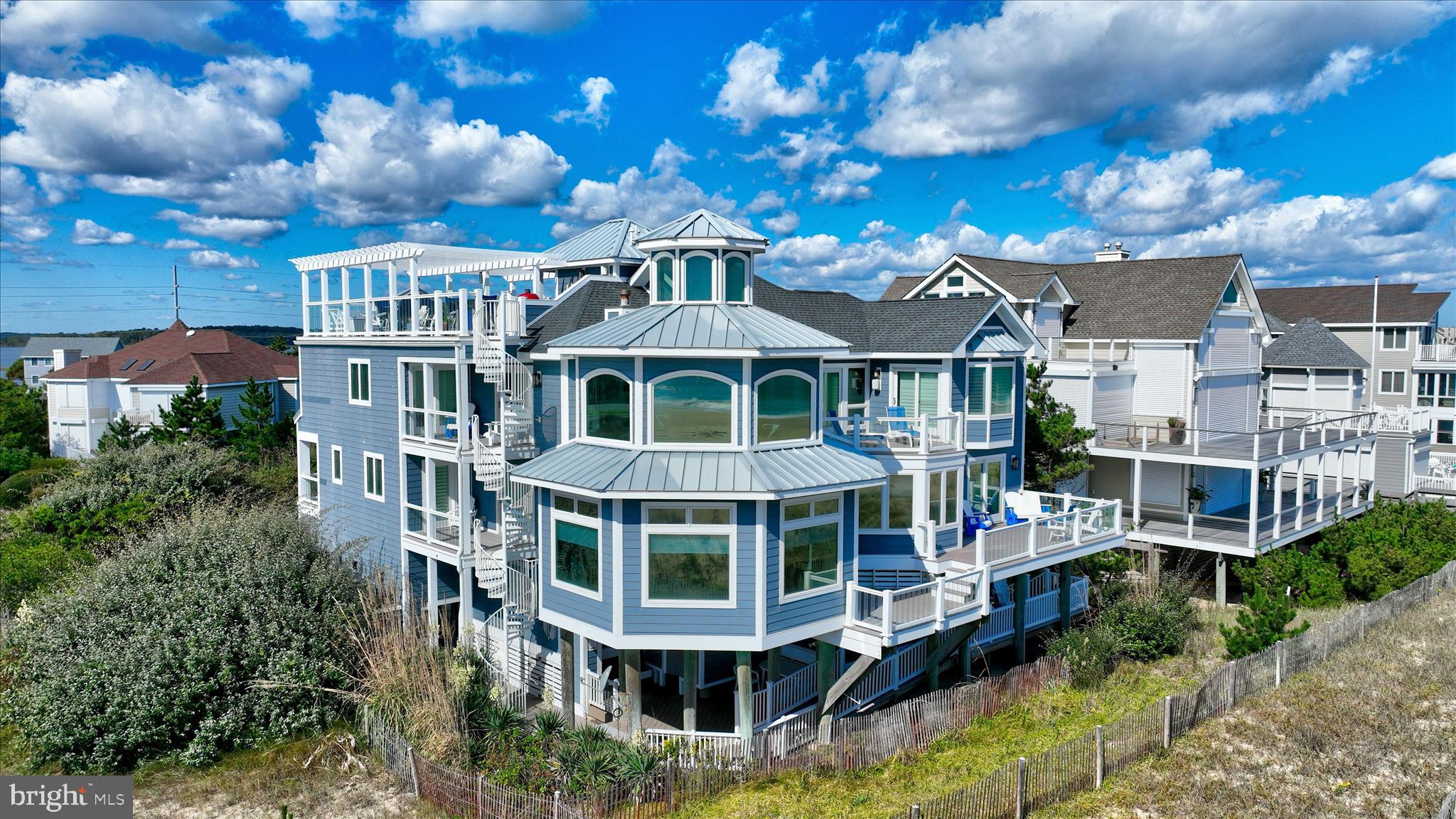 A Coastal Retreat on the Beach. Discover the coastal elegance of 40110 Owens Court, an extraordinary custom oceanfront home, perfectly nestled beside Fenwick Island State Park. This luxurious coastal retreat spans four levels, offering unparalleled living and entertaining spaces with breathtaking, panoramic views of the ocean, bay, and surrounding wildlife. Updated and expanded in 2017, this home combines modern luxury with timeless coastal charm. Key updates include a new roof, siding, hurricane-proof windows, expanded living areas, and enhanced outdoor spaces, complete with new decking, railings, and an elevator. Designed to immerse you in the beauty of the ocean and bay, natural light floods every corner of the home, creating a seamless connection between indoor and outdoor living. The 2nd floor is a celebration of oceanfront living, where expansive windows and multiple balconies frame the Atlantic’s stunning vistas. At the heart of this level lies the grand living room, crowned by a soaring two-story copula, offering an inviting space for gathering and entertaining while enjoying uninterrupted ocean views. The gourmet kitchen is a chef’s dream, equipped with top-tier appliances including a Wolf stove, Viking fridge/freezer, two dishwashers, and a wine bar. Granite countertops, custom 42" cabinetry, and a sprawling island with generous seating make this kitchen both functional and stylish. Adjacent to the kitchen, a cozy breakfast room offers additional display cabinetry and opens onto the balcony, perfect for morning coffee with ocean breezes. For grander occasions, the formal dining room provides an exquisite setting with the backdrop of the sea, while the family room, doubling as a theater room with surround sound, remote screen, and a fireplace, offers a cozy retreat for movie nights. This level also features two guest bedrooms, each with unique touches and access to private balconies, sharing a well-appointed bath, offering a tranquil retreat for family and friends. The 3rd level is dedicated to two luxurious bedroom suites. The primary suite is a serene sanctuary, complete with an office space, custom cabinetry, a spacious ensuite featuring a dual vanity and walk-in shower, and a private balcony offering serene bay and ocean views. The second suite is equally opulent, with a spa-like bath, access to the main deck, and breathtaking ocean views. A cozy sitting area between the suites provides the perfect nook for reading while surrounded by stunning scenery. Ascend to the rooftop deck and experience the ultimate outdoor living space. Complete with ample seating, a grill, refrigerator, dishwasher, and even a hot tub, it’s an entertainer's paradise. Enjoy the tranquil ambiance of the sunset over the bay, while music from the integrated sound system fills the air. With a half-bath and extra storage on this level, every convenience is at your fingertips. The 1st level of the home offers a separate two-bedroom apartment, each with ensuite baths, a kitchenette, family room, laundry center, and access to the deck and outdoor shower—ideal for guests to have their own private space during their stay. This home also features a handicap-accessible entrance and an elevator, ensuring easy access to many of its living levels. Parking is never an issue, with a beautifully hardscaped driveway that accommodates 8-10 cars, a two-car carport, and elegant landscaping. Located just a short bike ride from the heart of Fenwick Island, you'll enjoy easy access to charming restaurants, boutiques, and entertainment. Come and experience the ultimate oceanfront lifestyle at 40110 Owens Court—where luxury, comfort, and coastal living meet.