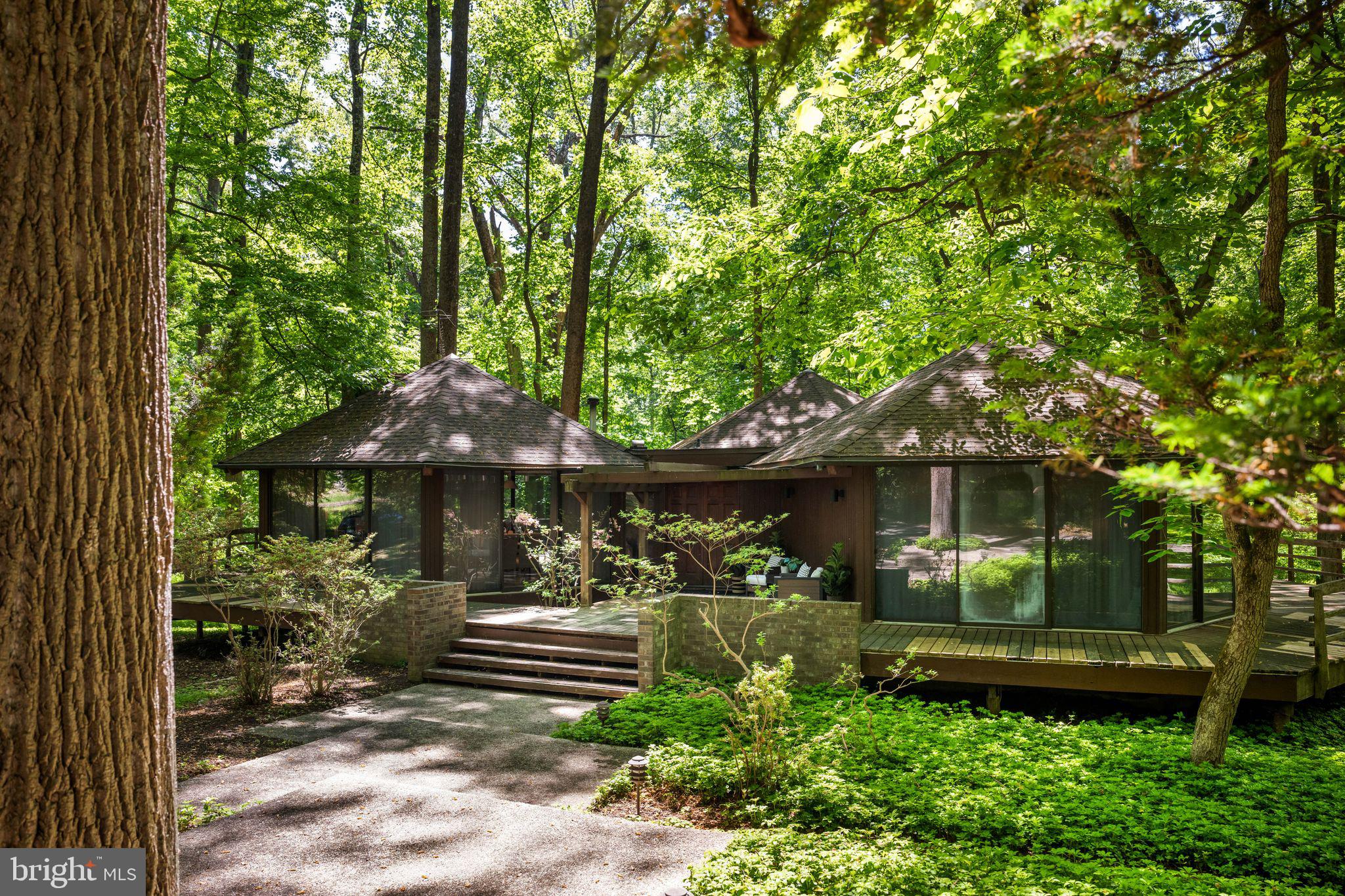 Tucked away on a private 2 plus acre wooded lot centrally located in the coveted Caves Valley, this one-of-a-kind architectural retreat is a celebration of creativity, nature, and timeless design. Composed of striking geometric hexagon pods, walls of glass, and fully wrapping decks, this distinctive deck tree house embraces its mid-century spirit while offering a living experience unlike any other. If you have ever dreamed of living in your own unique tree-house setting, with the utmost privacy, you have found the one. 

At the heart of the home, a dramatic great room and dining space soar beneath warm wood-paneled beam ceilings, anchored by a stunning wood-burning fireplace that draws the eye upward and invites gatherings both intimate and grand. Just beyond, a quintessential 1970s wet bar creates the perfect setting for entertaining and conversation.

The centrally located kitchen is thoughtfully designed for both form and function, featuring granite countertops, updated appliances, floor-to-ceiling cabinetry, impressive space saving built-ins, and direct access to the rear deck—ideal for grilling, dining beneath the trees, or enjoying a glass of wine with book in hand.

The home's additional two main bedrooms each feature ensuite bathrooms, wood vaulted ceilings, loft spaces, and oversized glass sliders connecting one with nature at every turn. A second great room doubles as a den, possible third bedroom, or home office, depending on ones needs, and inspires creativity and quiet reflection. It is complete with custom built-ins for the avid reader, a free-standing pellet stove, and an elevator that serves the lower utility level of the home. 

Designed for artists, visionaries, and those who seek a deeper connection to their surroundings, this remarkable residence frames ever-changing woodland vistas in every season—from the fiery hues of autumn to the lush greens of summer. 

Thoughtfully maintained and updated, the property includes many recent improvements including new flat and pod roofing (2024/2025), heating system (2023) and hot water heater (2024). 

Rarely does a home so beautifully blur the line between architecture and art. Beloved by the same family for several decades, the time has come for this special home's next steward to enjoy it not simply as a place to live, but a place to imagine, create, and thrive.