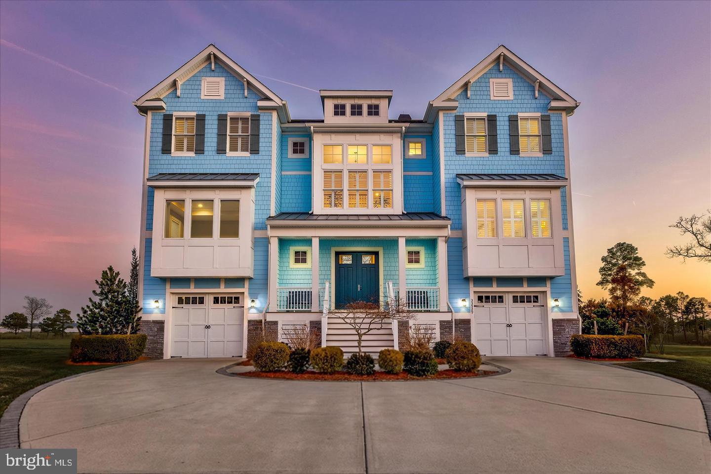 Elevated Bayfront Living in The Peninsula’s Premier Waterfront Setting

Perfectly positioned on a coveted waterfront homesite within the prestigious Sanctuary neighborhood, this exceptional coastal contemporary residence captures sweeping panoramic views of the Indian River Bay, protected wetlands, and championship golf course. Offering five bedrooms, five full baths, and one half bath, the home showcases refined architectural design, upscale finishes, and seamless indoor-outdoor living within one of Delaware’s most sought-after gated resort communities.

A grand double-door entry introduces a thoughtfully designed multi-level floor plan enhanced by hardwood flooring, custom millwork, designer lighting, and elevator access to all levels. The dramatic two-story great room serves as the centerpiece of the home, featuring soaring shiplap ceilings, a floor-to-ceiling quartz fireplace, remote-controlled window treatments, and an expansive wall of glass framing breathtaking sunsets and coastal wildlife views.

The chef’s kitchen was designed for entertaining and everyday luxury, complete with an oversized quartz island, 42-inch soft-close cabinetry, designer blue glass tile backsplash, gas cooktop, built-in microwave/convection oven, beverage refrigerator, stainless steel appliances, and statement pendant lighting. The adjoining dining area with custom wainscoting opens seamlessly to the screened porch, creating the ideal setting for sophisticated coastal entertaining.

Privately situated on the main living level, the owner’s suite offers a tranquil waterfront retreat with tray ceiling lighting, private balcony access, dual walk-in closets, and a spa-inspired bath featuring a freestanding soaking tub, oversized frameless glass shower, dual vanities, plantation shutters, and private water closet. A dedicated office with built-in window seating and granite-topped storage, along with a powder room, complete the main level.

The lower level is designed for recreation and guest accommodations, featuring a spacious entertainment lounge with wet bar, concealed refrigerator, wine storage, bonus flex room with atrium pocket doors ideal for a fitness studio or media room, guest suite with Jack-and-Jill bath, mudroom with custom built-ins, and access to two separate garages. Sliding glass doors open to an expansive hardscaped terrace with grilling station, porch swing, and multiple outdoor living spaces overlooking the bay, wetlands, and fairways.

The upper level includes a loft with balcony access and three generously sized en suite guest bedrooms, each with walk-in closets. One guest suite offers its own private waterfront balcony with stunning water views.

Residents enjoy a private gated resort lifestyle centered around the acclaimed Jack Nicklaus Signature Golf Course and an unmatched collection of luxury amenities. Community offerings include indoor and outdoor pools, an adults-only heated pool, wave pool, full-service spa, state-of-the-art fitness center, tennis and pickleball courts, nature trails, private bay beach, fishing pier, miniature golf, dog park, clubhouse dining, golf lounges, and scenic waterfront recreation.

Ideally located near Lewes and Rehoboth Beach, this extraordinary waterfront residence delivers the ultimate blend of refined coastal design, championship golf, resort-style amenities, and elevated living along Delaware’s premier waterfront corridor.