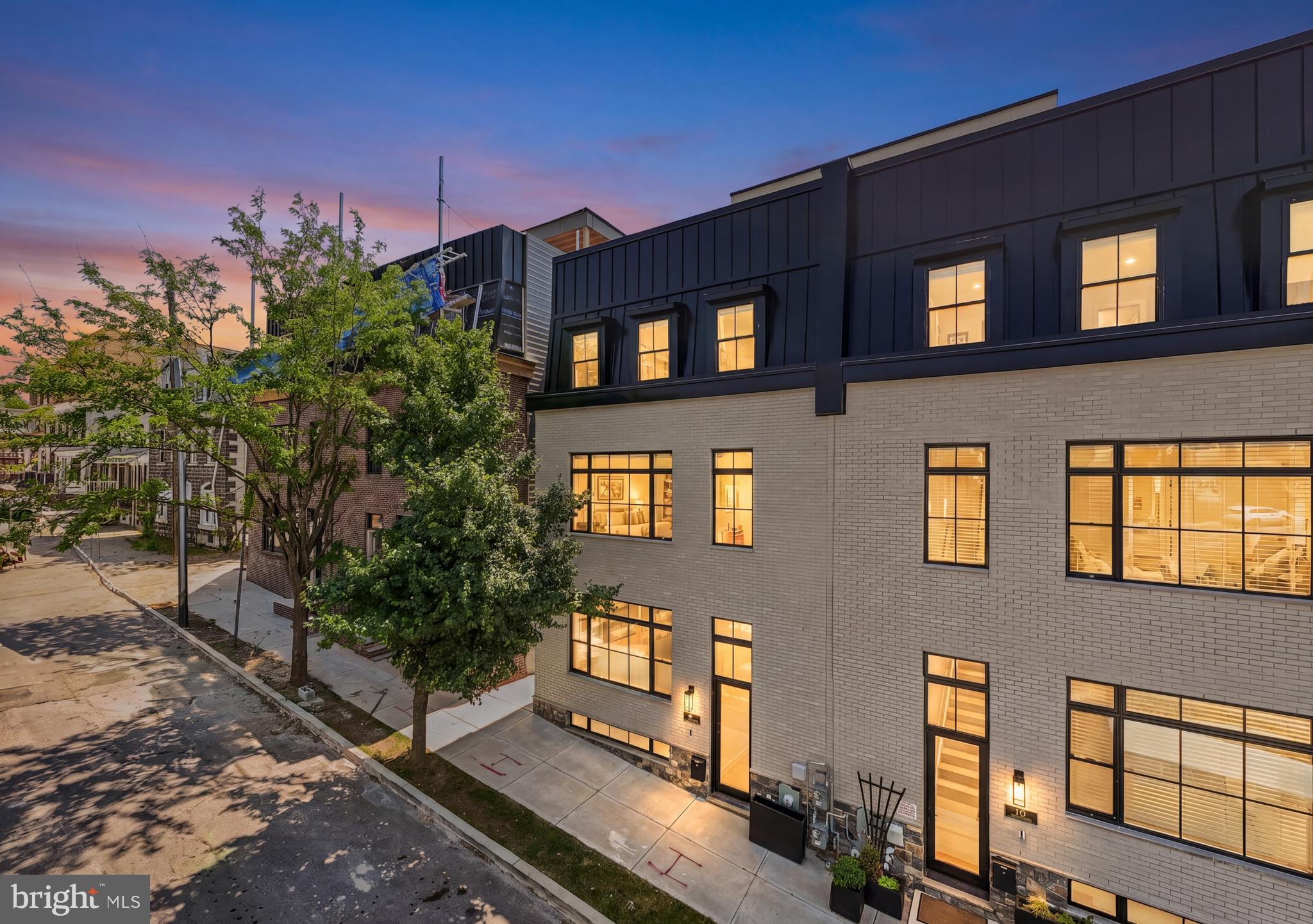 206 Kalos Street delivers the rare combination of luxury new construction, thoughtful designer upgrades, and one of Philadelphia’s most connected outdoor lifestyles — all tucked within the coveted Wissahickon/Manayunk corridor. Built less than a year ago and benefiting from a full 10-year tax abatement, this expansive townhome offers nearly 4,000 square feet of elevated living space, a two-car garage, multiple outdoor retreats, and panoramic skyline views that redefine city living.
Inside, the home immediately sets itself apart through its custom designer finishes and layered details - well beyond standard builder selections. Wide open-concept living spaces create seamless flow between the dining area, chef’s kitchen, and family room, while oversized windows flood the home with natural light. The kitchen serves as the centerpiece of the main level, anchored by an extraordinary 15+ foot quartz island, a custom handmade range hood, pot filler, two oversized pantry spaces, and a live-edge wood bar with beverage fridge. Just off the family room, a private deck creates effortless indoor-outdoor entertaining space.
Throughout the home, you’ll notice custom craftsmanship that adds depth and character at every turn — including elegant board and batten wall detailing spanning multiple levels, fluted wood accent walls, designer grasscloth wallpaper, custom built-ins and window treatments, and elevated lighting sections in the dining room, entryway, kitchen, and primary suite.
The lower level offers finished living space directly connected to the attached two-car garage — ideal for a secondary lounge, fitness space, media room, or office. The entire second level features a spacious private office with French doors and floor to ceiling windows, a primary suite with a professionally customized walk-in closet, expansive en-suite bath with large walk in shower, soaking tub, and double sinks with vanity and a separate laundry room for owner’s convenience. 
You’ll find three additional bedrooms on the 3rd level, one with a private en-suite and two that have walk in closets and share a full hall bath.  The top level was designed for entertaining and unforgettable skyline moments. A custom entertaining bar featuring quartz countertops, a beverage fridge, cabinets and live-edge wood shelving services the expansive rooftop deck, where sweeping 365-degree views extend from the Center City skyline to the surrounding treetops and rolling hillsides.  Whether hosting friends at sunset or enjoying a quiet evening under the city lights, this rooftop experience feels truly exceptional.
The location offers an unmatched blend of nature, walkability, and accessibility. Situated just one block from the Wissahickon Train Station and the entrance to Wissahickon Valley Park’s trail system, the home provides immediate access to miles of trails, biking, hiking, and outdoor recreation. Enjoy a walkable stroll to Main Street Manayunk’s restaurants, shopping, coffee shops, and nightlife, along with nearby favorites including Pencoyd Landing, the Cynwyd Heritage Trail, and award-winning Lark restaurant. With easy access to Center City, Kelly Drive, the Philadelphia Airport, and all your favorite shore points, 206 Kalos Street offers a lifestyle that seamlessly blends luxury, convenience, design, and connection to both nature and the city.