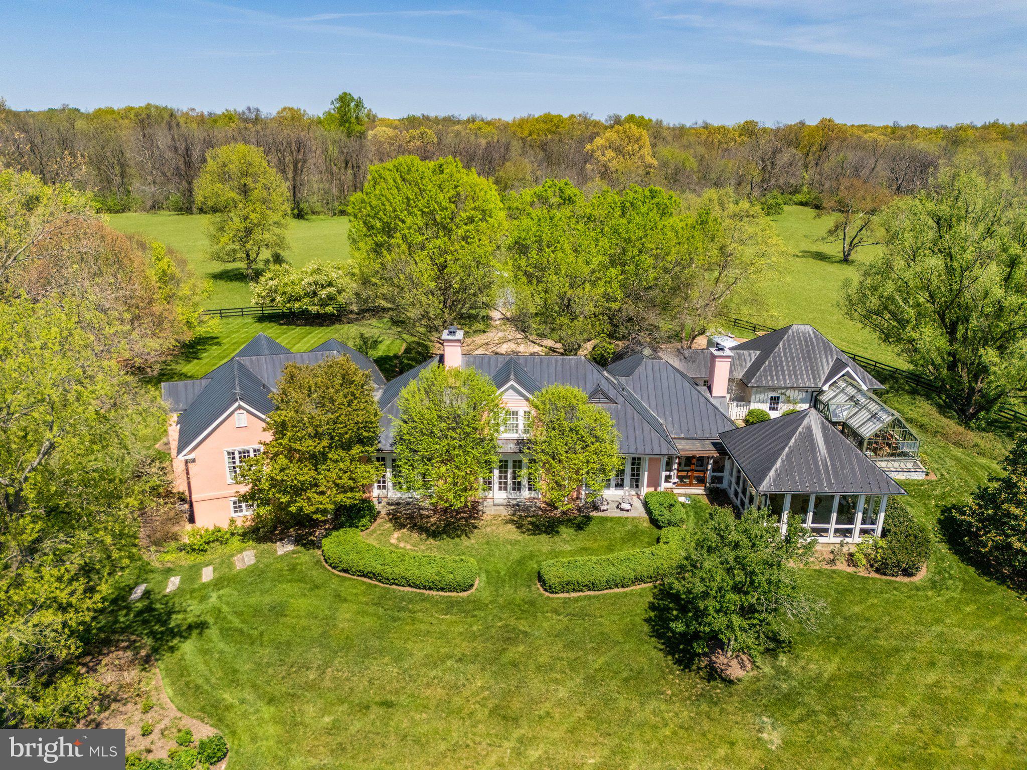 “Salterhill” sits atop a knoll in the heart of 145 acres, offering sweeping views of the Blue Ridge Mountains. Designed by Charlottesville architect Jay Dalgliesh and built in 1989 the 7,000+ sq ft home features 6 bedrooms, 5 full baths and 2 half baths. The farm spans two parcels beautifully blending open hay fields and mature hardwood forest. Surrounded by large farms protected by conservation easements, Salterhill remains unencumbered and offers tax credit potential as well as having four additional dwelling unit rights. A winding drive through the woods and over two cattle guards lead to a pea gravel courtyard framed by trees and mature landscaping. A flagstone path welcomes guests to the mahogany double doors. Inside, a curved front hall with Zuber French woodblock wallpaper panels opens to the light-filled living room, where a fireplace and a wall of windows showcase the southern views. The formal dining room, with chair rail and intricate moldings, flows seamlessly from here. The gourmet kitchen, remodeled in 2021, features a tray ceiling, large island and an adjoining family room anchored by a floor to ceiling Albemarle greenstone fireplace. Off the kitchen hallway are a wet bar, gardening nook with antique soapstone sink and a powder room. In the back hallway, which connects to a two-car garage, are large pantry closets.  A four-season room with interchangeable screens and glass panels offers year-round enjoyment of the views.  The main level also includes a pine paneled library with fireplace and passage to the primary suite.  The luxury primary suite has built-ins, large bath with dual vanities, dressing table and separate walk-in closets. There are two more-bedroom suites, laundry room and powder room.  Upstairs a guest suite with full bath and walk-in closet is joined by attic storage.  The walk-out lower level offers two more bedrooms with a Jack & Jill bath, a spacious recreation room, full kitchen, and private entrance—ideal for guests or an in-law suite.  The original landscape plan was done by the renowned landscape architect, the late Meade Palmer.  More recent changes and additions have been made by Nicole Seiss of LanDesign.  Nature lovers will appreciate the magnolia, sycamore, pin oak, beech, red maple, weeping willow, and horse chestnut trees, as well as two large perennial beds.  The Hartley Botanic greenhouse from England and tiered vegetable beds enhance the property’s charm.  Perfectly located – within the historic Blue Ridge Hunt territory, 10 minutes to the Virginia State Arboretum and Shenandoah River, 20 minutes to Sky Meadows State Park, 50 minutes to Dulles International Airport and 90 minutes to Washington, D.C.