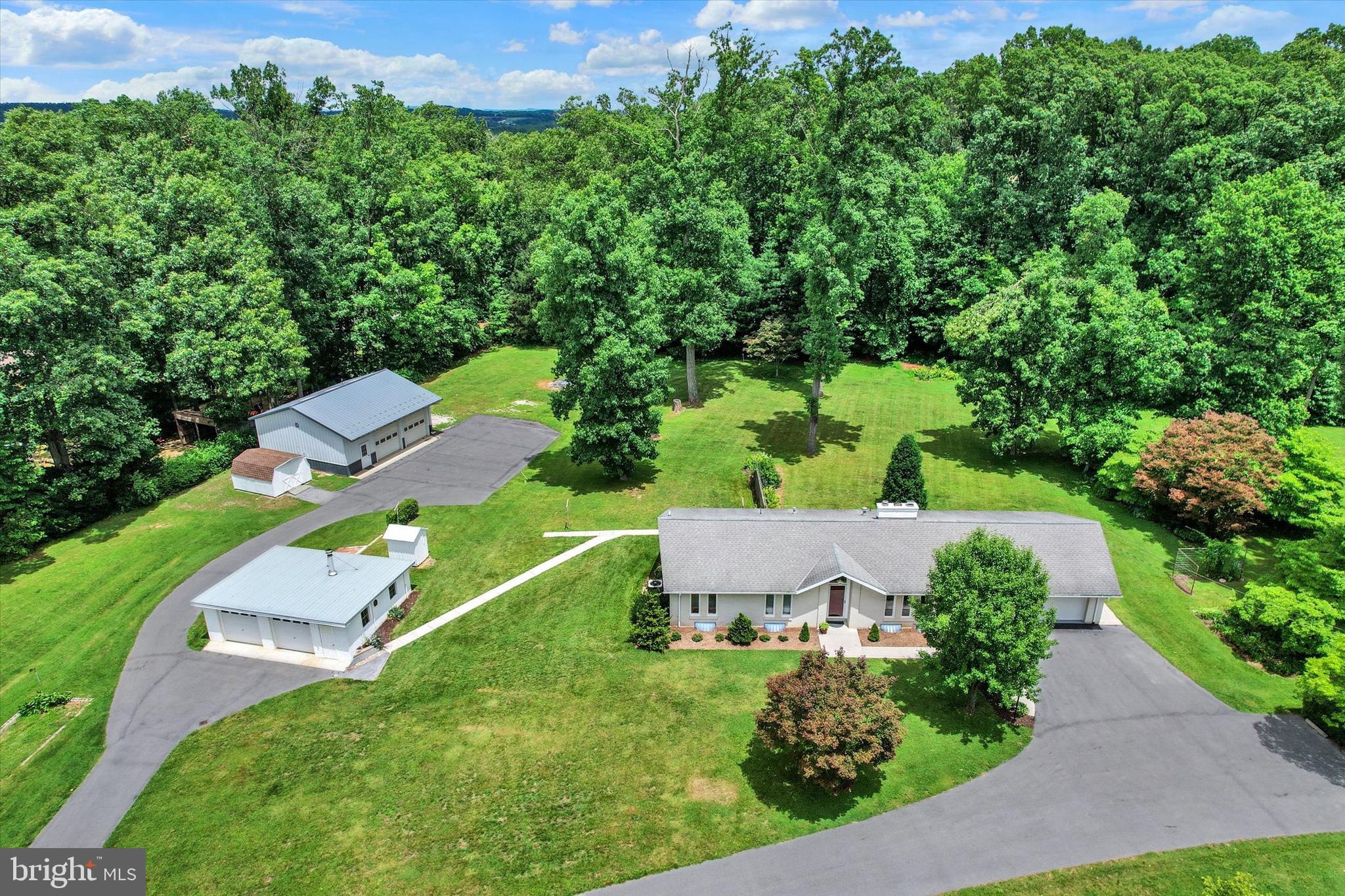 Live, work, create, and unwind from one exceptional Spring Grove property, gracefully positioned on three pristine acres of scenic countryside with no HOA. A true private retreat, this custom brick ranch evokes a sense of peace, presence, and possibility from the moment you arrive. Mature landscaping, open lawn, wooded views, and a private rear setting create an atmosphere of quiet luxury, where everyday living feels beautifully connected to nature.

Picture a slow Saturday morning with coffee in hand, listening to the gentle sounds of the countryside from the rear patio as the property unfolds around you. With three picturesque acres to enjoy, adjacent to a 130-acre wooded township park and just a short drive to Codorus State Park, this setting offers exceptional access to hiking, boating, fishing, horseback riding, camping, and year-round outdoor recreation. Peaceful and private, yet convenient to Route 30, I-83, Hanover, York, Maryland and surrounding areas, the location offers the best of country living with everyday accessibility. Located in Heidelberg Township’s Rural Resource Area-Agricultural zoning, which allows horses for non-commercial purposes, the property offers beauty, privacy, and long-term versatility.

Designed with both elegance and functionality in mind, the garage and outbuilding package is truly exceptional. In addition to the attached two-car garage, there is a detached two-car garage and an impressive 30' x 34' Morton pole building with propane heat, bathroom with sink/urinal, hot and cold water, office/workshop area, electric throughout, full-length storage platform, and second-floor storage access. The expansive paved driveway and parking areas provide room for campers, boats, work trailers, equipment, recreational vehicles, and guests. Whether you are a contractor, entrepreneur, car enthusiast, woodworker, collector, landscaper, hobbyist, or someone who simply values space and capability, this property adapts beautifully to your vision.

Inside, the home is warm, refined, and thoughtfully updated, offering three bedrooms, two full baths, a spacious living room, and a stunning remodeled kitchen designed for both everyday comfort and effortless entertaining. The kitchen showcases sleek white cabinetry, upgraded countertops, tile backsplash, stainless steel appliances, cooktop, wall oven, large island with seating, built-ins, abundant storage, and a dining area overlooking the rear patio and backyard. The lower level expands the living space with a family room featuring a brick fireplace with wood-burning insert, a game/craft room, laundry/workshop area, second full bath, and generous storage.

Recent documentation reflects thoughtful care and stewardship, including a septic system installed in 2019 and recently inspected and pumped, recent boiler service, a new 275-gallon interior Roth double-wall oil tank, completed electrical and plumbing updates, water testing, roof inspection documentation, and pest treatment documentation available for buyer review.

This is more than a home; it is a distinguished lifestyle property where comfort, capability, privacy, and opportunity come together with rare balance. For those who value space, flexibility, and long-term potential, this remarkable Spring Grove retreat offers the freedom to live beautifully, work efficiently, create without limits, and enjoy the serenity of country living every day.