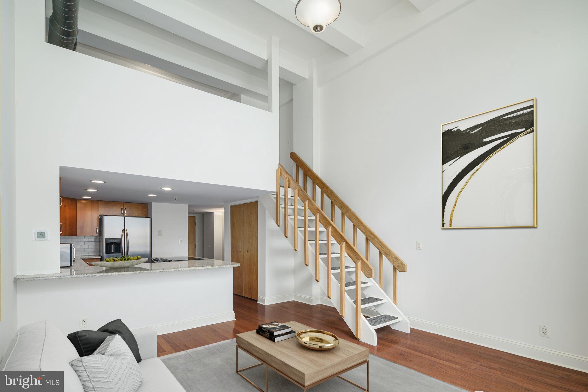 Unit 106A is a bi-level 1-bed, 1.5-bath that offers main-level living, dining, kitchen, and half bath with a second-level lofted bedroom and full bath. The 20' high ceilings create a spacious and airy ambiance and allow for the oversized floor-to-ceiling window, which floods the unit with natural sunlight. As if that's not enough, the HVAC system and water heater are only a few years old, making this unit move-in ready! This unit includes one assigned and deeded GARAGE PARKING space! Building amenities include a 24/7 front desk, a large on-site fitness center, and a central landscaped courtyard with a koi pond and seasonal lounge area. Access and convenience are stellar, with grocery, retail, and transit all within one half-block and positioned near Center City and many popular South Philly neighborhoods, including Graduate Hospital, Newbold, Bella Vista, Passyunk Square, and East Passyunk. Some photos are virtually staged.