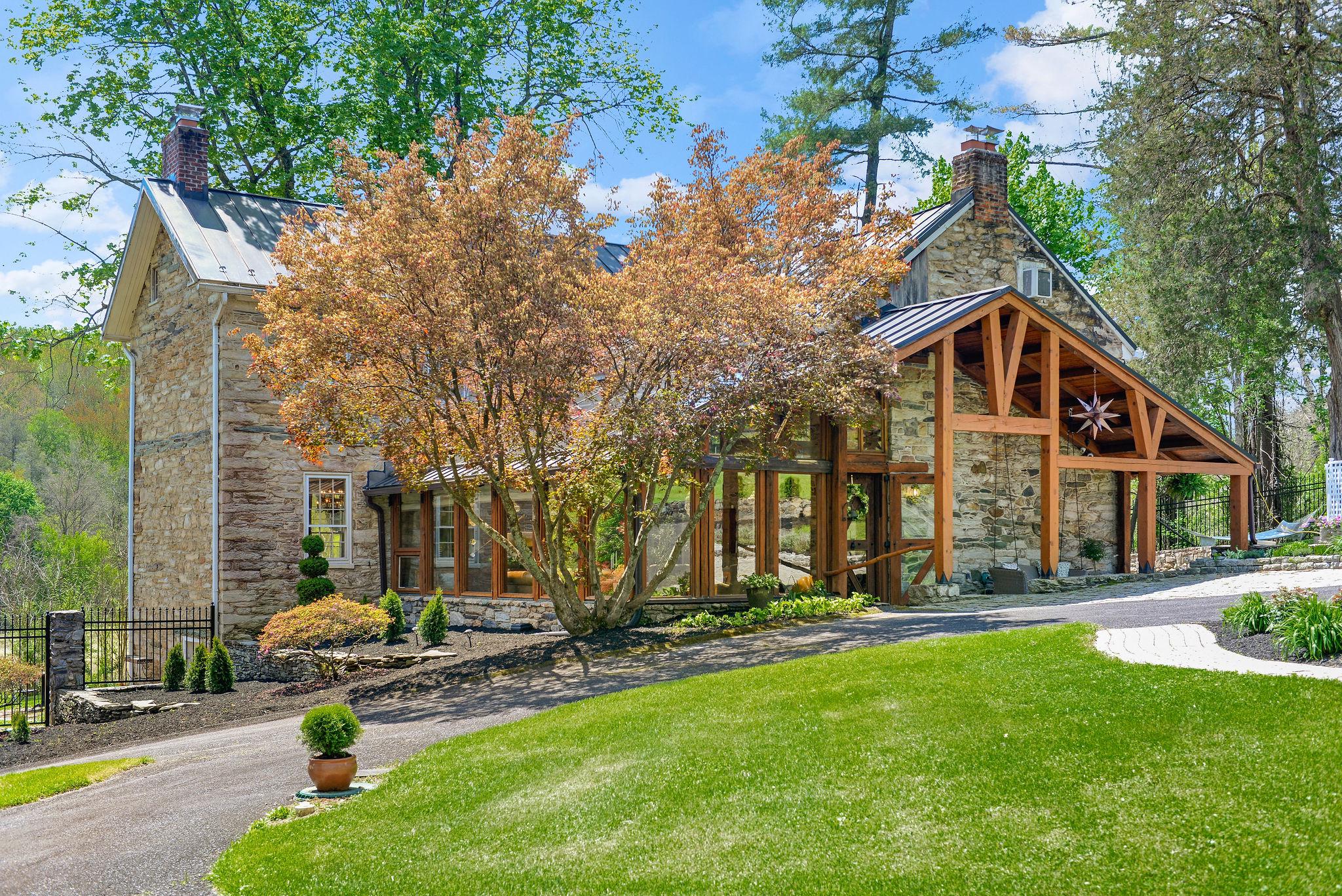 Lorien at Avignon | A Rare Frederick County Estate
Once home to acclaimed author and Egyptologist Barbara Mertz—known worldwide through the pen names Elizabeth Peters and Barbara Michaels—Lorien at Avignon stands today as one of Frederick County’s most extraordinary historic estate offerings.
Set on over 10.24 scenic acres along picturesque Linganore Creek, this distinguished three-story Georgian stone residence, circa 1820, is recognized by the Frederick County Landmarks Foundation and showcases enduring craftsmanship, locally sourced stone construction, and preserved period detailing.
Thoughtfully restored and enhanced as a long-term residence, the property was never intended for resale and is now unexpectedly available due to a change in circumstances.
Inside, soaring ceilings, abundant natural light, restored original floors, and four working fireplaces create interiors rich in warmth and character. A dramatic solarium overlooks the gardens, while the renovated kitchen features quartz countertops, updated systems, and refined finishes that bring modern comfort to this remarkable home.
The estate offers rare everyday livability with three-zone central air conditioning, multiple heating sources, two wells, and infrastructure designed to support both home and grounds.
Outdoors, Lorien unfolds as a private sanctuary of elegant and whimsical beauty. Mature perennial gardens bloom throughout the seasons, winding paths lead to water features and gathering spaces, and the grounds include a restored gazebo, orchard, apiary, and a half-acre vineyard of Bordeaux varietal grapes currently maintained by experienced caretakers.
Two ponds joined by a waterfall, a reflecting pool inspired by Hadrian’s Villa, custom outdoor stone fireplace, and creek access just steps from the home create an atmosphere rarely found and nearly impossible to replicate.
Whether envisioned as a full-time residence, luxurious weekend retreat, creative sanctuary, or hospitality-inspired opportunity (buyer to verify intended use), Lorien offers a lifestyle few properties can match.
Optional furnishings available for a turnkey transition.. A curated selection of furnishings, décor, and functional elements is available separately, offering the opportunity for a seamless, turnkey transition. Thoughtfully chosen to reflect the character and rhythm of the estate, these pieces allow the next steward to step directly into the lifestyle Lorien has been designed to hold, where every space feels considered, cohesive, and ready to be lived in from day one.
A property of history, beauty, stewardship, and soul—ready for its next steward.