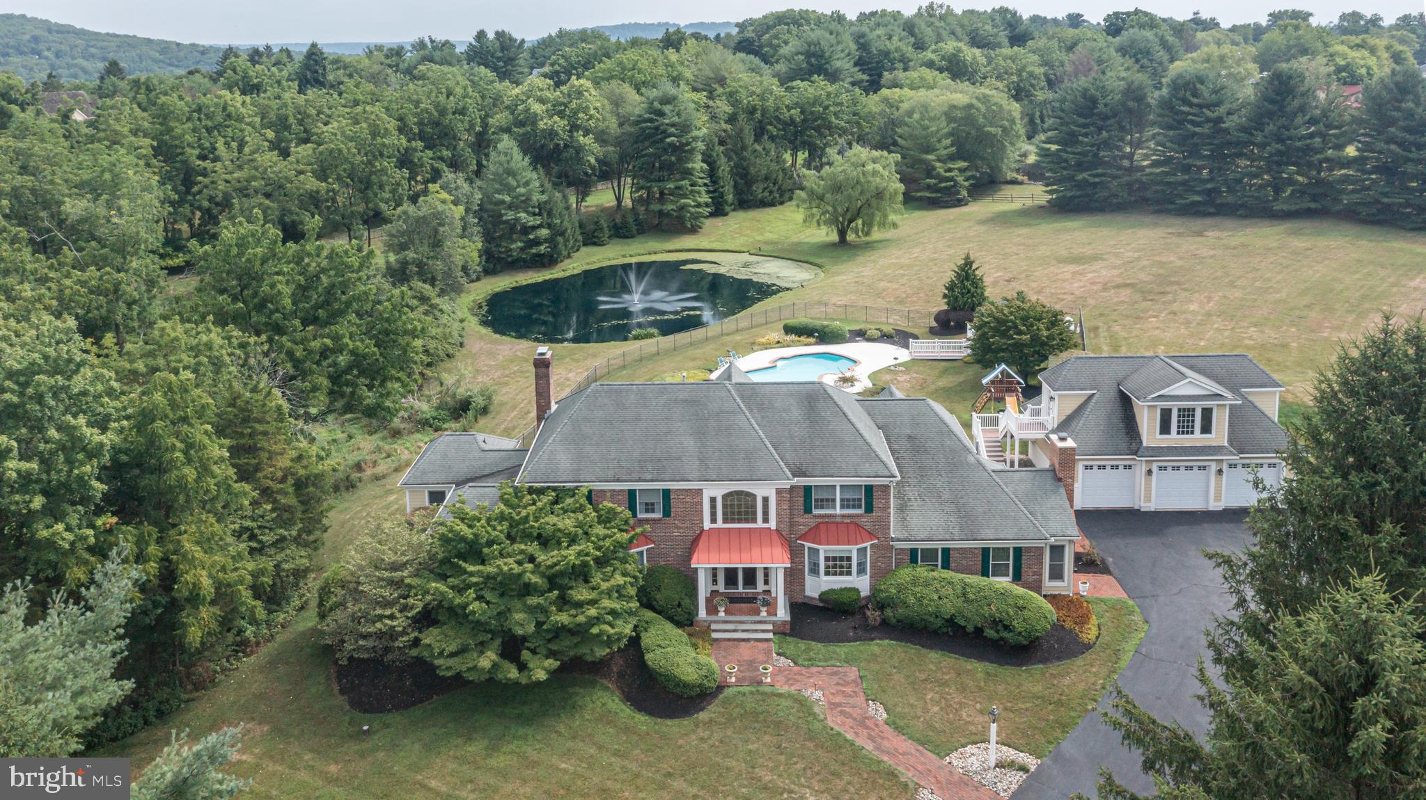 Discover thoughtfully designed renovations performed by one of the top Upper Makefield, Bucks County builders, Worthington Custom Builder with an uncompromising level of quality at 1089 Eagle Road. A stunning center hall colonial home nestled on nearly 5 acres of lush landscape down a long, no outlet paved and Belgium-blocked trimmed road to a private enclave of 3 custom homes offering peaceful picturesque pond views. Numerous interior upgrades, an expansive 3-car detached garage with a completely framed carriage house or mother-in-law suite above presenting the best views of the property, and a backyard oasis with desirable seclusion have turned this property into a true forever home. As you enter this well-maintained home, you will appreciate the stunning hardwood floors guiding you throughout the main level in a circular flow. The formal living and dining rooms, perfectly balanced on either side of the foyer flaunting an eye-catching curved staircase make for a welcoming introduction. No expense has been spared in options and improvements are evident in the beautifully planned Gourmet Kitchen with its contrasting color sprawling island with prep sink, professional Wolf 6-burner gas stove and double oven, granite counters, abundance of rich cabinetry including custom wood paneled freezer and refrigerator with separate cooling drawers, 2 pantries, and spacious breakfast area flooded with natural light from its wall of windows and skylights. Family and friends have a choice of rooms to be entertained in from the cozy open concept family room with gas-burning fireplace and coffered ceilings throughout to the connecting skylit sunroom thru several sets of paned French doors and the exquisite sunken den with built-in bar, gas fireplace, beam decorated coffered ceiling and custom built-ins. A back wing leads to a corner first-floor master bedroom with a private deck, backyard access and a neighboring full bath ideal for guests and/or convenient first floor living. Completing this level is a half bath, private study ornamented with rich custom built-in cabinetry and bookshelves throughout and a laundry/mud room with outdoor access. Upstairs, the primary suite boasts a lovely sitting room and two spacious walk-in closets with organizers, making it a luxurious retreat with beautiful views out of every window. The marble decorated bath features a private water closet with walk-in shower, dual sink vanity, jetted tub, all designed with timeless elegance. Three additional bedrooms found on this level are generously sized and share a full hall bathroom. As you descend to the finished lower level via the kitchen or den, one can appreciate the abundance of living and storage space including a game room with built-in wet bar, full kitchen suite, sitting/exercise room, a full bath and a dual exit door sub cellar for storage or landscaping equipment. One of the home's stand out features is its amazing outdoor living space showcasing an in-ground freeform pool, pond with aerator fountain and separate well, pool house with bath, sizeable brick terrace, acreage and complete privacy provided by trees and exiting to Eagle Road literally across from the Upper Makefield Police Department. Additional amenities include the unfinished carriage house space above the garage with roughed-in plumbing for even more versatile living space, new pool coping, outdoor sound system, brick walkways, fish stocked pond and on a quiet cul-de-sac. Minutes from downtown Newtown, New Hope and a quick access to the Princeton area in NJ including access to the I-295 corridor. This home importantly offers easy access to great eateries, shops, and ideally situated within walking distance to Sol Feinstone Elementary School and within the sought-after award-winning Council Rock School district. This magnificent country estate is a must see!