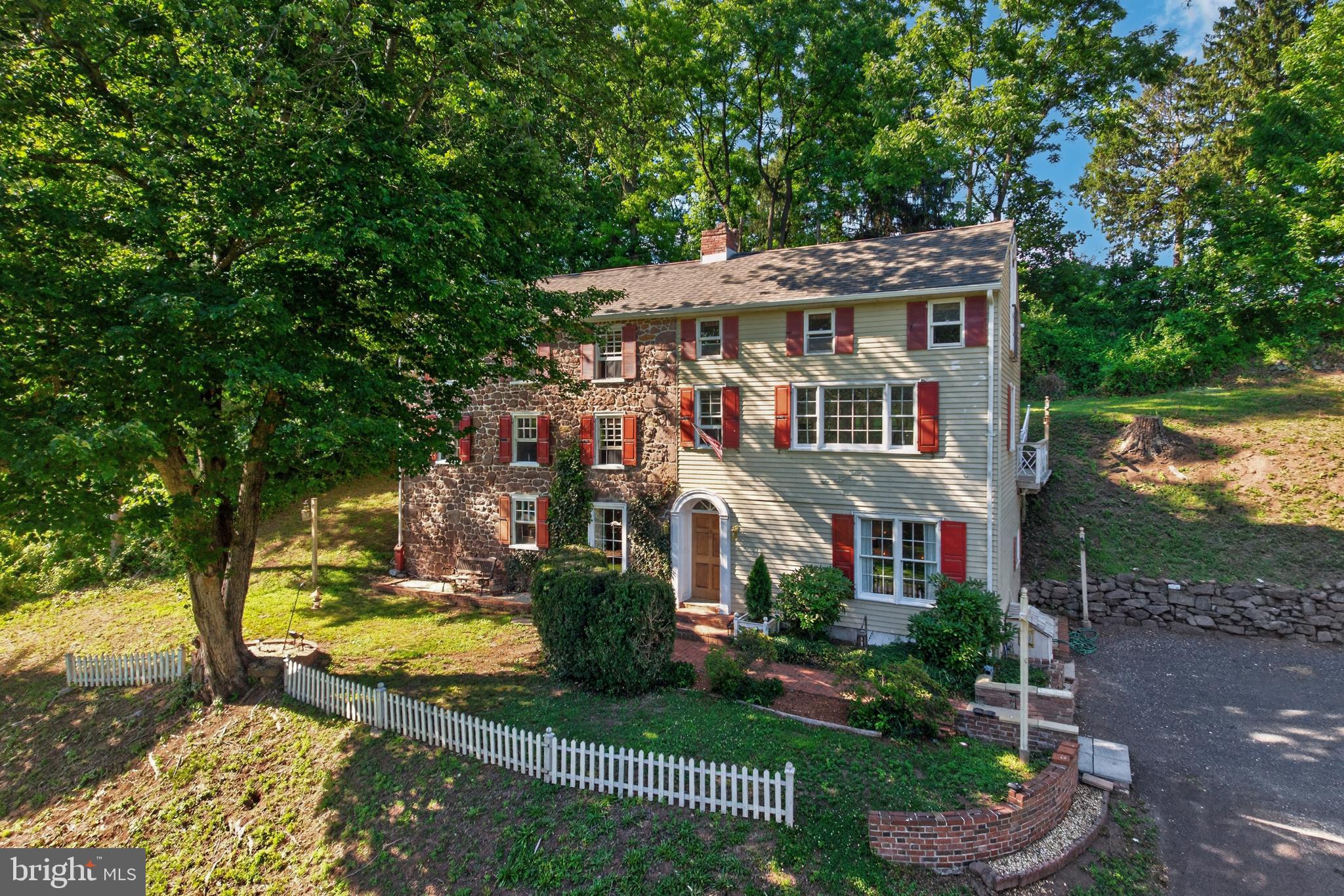 Constructed of beautiful Pennsylvania fieldstone and filled with distinctive architectural details, this extraordinary property offers a rare opportunity to own a piece of history while enjoying scenic beauty, modern conveniences, and timeless character.  Originally built in 1801 and thoughtfully expanded over the years, this remarkable home showcases the craftsmanship, character and enduring beauty of a bygone era. 

A herringbone brick path leads to the welcoming entrance hall with the custom-built staircase.  To the right French doors open into the Dining Room with custom crown molding, wainscoting, and built in storage along one wall and natural light flooding the room with warmth.  

At the end of the hall is a full bath with a walk in shower and full size whirlpool tub. The dryer is closeted in the bathroom while the washer is under the hall stairs.

The oldest part of the home is the gathering room to the left, complete with beamed ceilings, hardwood floors and a stunning original brick and stone wood-burning fireplace with a custom-built mahogany surround.  Who doesn’t love a glowing fire in the fireplace on those cold winter nights?  The kitchen, with oak cabinetry, overlooks this focal room.  

Throughout the home you will discover beautiful oak and original wide plank pine floors, oversized windows that fill rooms with natural light, a striking steel spiral staircase and an elegant fireplace framed by a finely crafted wood mantel.

A stand out of the home is the spacious second floor living room.  An oversized window provides a panoramic view where you can savor the bucolic surrounding woods, fields and the meandering Pigeon Creek in the background    Music enthusiasts will appreciate the built-in stereo amplifier and speakers that serve the living and dining rooms, all included with the home.   French doors open to a spectacular 16 x 13 private deck featuring both covered and open-air spaces, complete with electric and a wet bar – perfect for entertaining or simply unwinding after a full day.  Note the dedicated 6000 watt generator independently wired to power the kitchen and family/gathering room. 

The primary bedroom suite provides a cozy retreat with its own wood-burning fireplace and an exit to the second level at the back of the house   Stairs continue to a 3rd level with another suite of rooms similar in configuration to the primary suite.  An attic/storage area is above this level.  
Take the spiral stairs to the upper level loft with built in mahogany bookcases.  A glass door opens to amazing views from this third floor.  A convenient half bath serves this level.
The detached two-story garage provides ample parking and an impressive workshop recently rewired including 240 volt electrical service.  An above ground pool, deck and pool house/cabana with stereo system is included with the property   The pool was opened and fully functional four years ago.  Today's status is unknown.  PLEASE NOTE:  The pool decking needs repair (as stated in seller’s disclosure).   It is not to be walked on.  Access to the entire pool area is off limits for showings.  
Sitting well back from a quiet country road, this property offers an exceptional sense of privacy and tranquility.