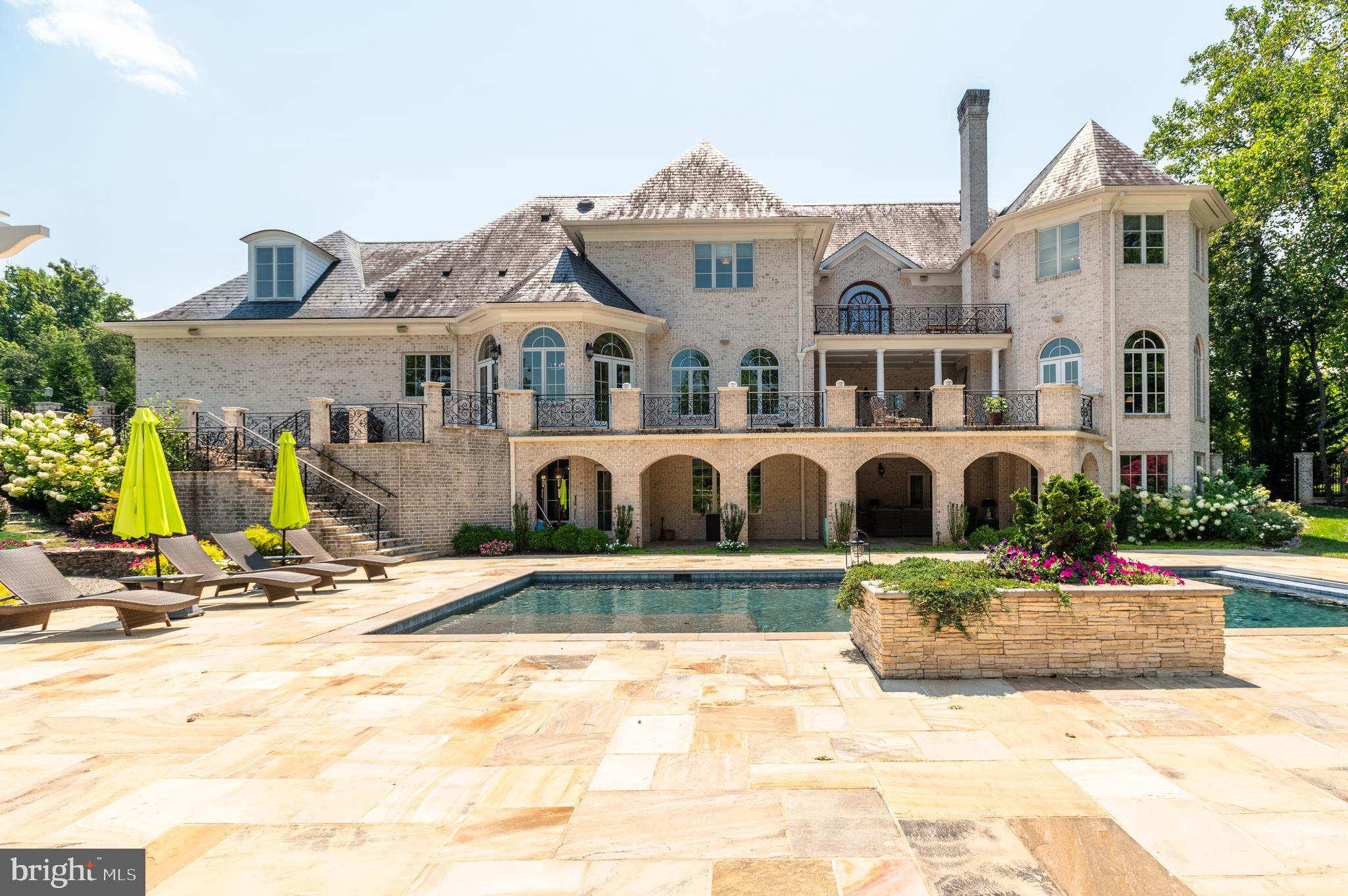 Located in the heart of Potomac Village, just two blocks from shops and restaurants, this exceptional residence epitomizes a flawless blend of architectural brilliance, high-end finishes, and modern amenities. Designed by an award-winning architect and completed in 2011, this luxurious home masterfully integrates timeless elegance with contemporary comforts. Spanning over 11,000 square feet across three meticulously finished levels, it offers grand scale living and entertaining, while also providing a warm, inviting interior thoughtfully designed for the comfort and enjoyment of family and friends.  The MAIN LEVEL is anchored by a stunning  front-to-back foyer, where a magnificent staircase with handcrafted wrought iron balustrades sets a welcoming ambiance for the owners and visitors.  The formal living and dining rooms exude sophistication, while the chef’s kitchen, with its high-end custom cabinetry and top-of-the-line professional style appliances, stands as the heart of the home. A spacious walk-in pantry and a convenient butler’s pantry enhance the functionality of this culinary haven. Adjacent to the kitchen, a spacious family room with walls of windows and a gas fireplace provides a perfect space for everyday activities. The stunning mahogany-paneled library features built-in bookshelves, a coffered and hand-painted ceiling, a gas fireplace and offers a serene retreat for work, reading, or quiet reflection. Tucked at the end of the hallway, the main level guest bedroom with an en-suite bath ensures that visitors enjoy both comfort and privacy.  Many of the main level rooms beautifully flow outside onto the expansive terrace through an array of oversized French doors creating an ideal setting for outdoor dining and entertaining. The UPPER LEVEL features four generously sized en-suite bedrooms, including the luxurious owner’s suite. This retreat boasts a spa-like bathroom, two walk-in closets, and access to a private balcony overlooking lush gardens. An additional bonus room/bedroom on this level offers flexible use, whether as a studio, office, or a bedroom. The WALK-OUT LOWER LEVEL is tailored for both entertainment and relaxation, featuring a state-of-the-art home theater, various gathering spaces, and a custom-designed bar that creates a vibrant, club-like atmosphere. It also includes two en-suite bedrooms, perfect for accommodating guests or serving as a versatile space for an in-home gym.  OUTSIDE, the property continues to impress with two large loggias featuring wood-burning fireplaces, a sleek black-bottom swimming pool, and amazing waterfalls. The garden is truly exceptional and arguably one of the most stunning in Potomac.  Its charm and allure are truly beyond words—be sure to check out the photos to fully appreciate its breathtaking beauty!
