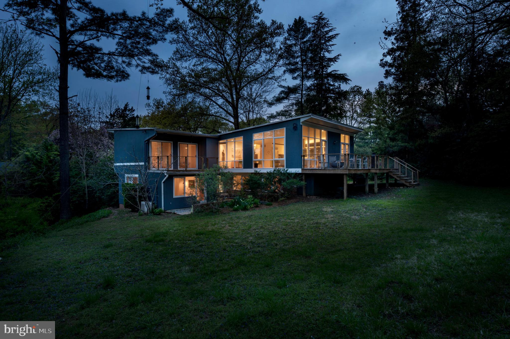 One of the premiere properties in the highly sought-after Hollin Hills neighborhood, this mid-century modern masterpiece sits on a beautifully landscaped half-acre lot. Designed by the renowned architect Charles Goodman and originally built for respected builder Robert Davenport, this home is a stunning blend of architectural history and thoughtful modern upgrades. A spectacular remodel has preserved its original charm while enhancing functionality and style. The home welcomes you with a light-filled foyer featuring a large picture window and custom coat closet. A dramatic, extra-wide oak staircase leads to the upper level, where a soaring butterfly roof defines the great room that is surrounded on three sides by walls of windows. This expansive space includes Italian custom oak and white cabinetry, a striking 13-foot island perfect for entertaining, corian countertops, high-end stainless appliances including new Sub-Zero refrigerator, expansive living room and a distinct dining area, all flowing effortlessly into the outdoors. Indoor and outdoor living are seamlessly integrated, with a side deck and a full-width rear deck that overlooks a large, flat backyard—ideal for gatherings or quiet relaxation. A half bath conveniently serves guests. 

The entire front half of the upper level is dedicated to a luxurious and private primary suite. It features soaring ceilings, an art studio or home office with built-ins, walls of windows, and sliding glass doors opening to the deck. An illuminated hallway with an 8-foot slit light and custom closets, including a large walk-in, leads to the spacious bedroom, an additional closet, and double sliding glass doors to a private yoga deck. The spa-like bathroom is lit by a row of clerestory windows and a skylight. Showcasing a floating Italian vanity, a glass walk-in shower with dual shower heads, and custom tile finishes.

The main level includes a beautifully designed in-law suite that offers a private bedroom with its own exterior entrance to a patio area and a fully remodeled bathroom with a sleek shower and custom tile. Additional rooms include a large family room with a wall of built-in storage and under-stair storage, two additional bedrooms, and a full bath enhanced with Norwegian wood paneling. 

High-end finishes and minimalist details are found throughout the home, including custom lighting, recessed and directional art lights, doors with negative space instead of traditional trim, and L-shaped brushed steel door handles. All major systems have been updated within the last few years, making this architectural gem truly move-in ready.