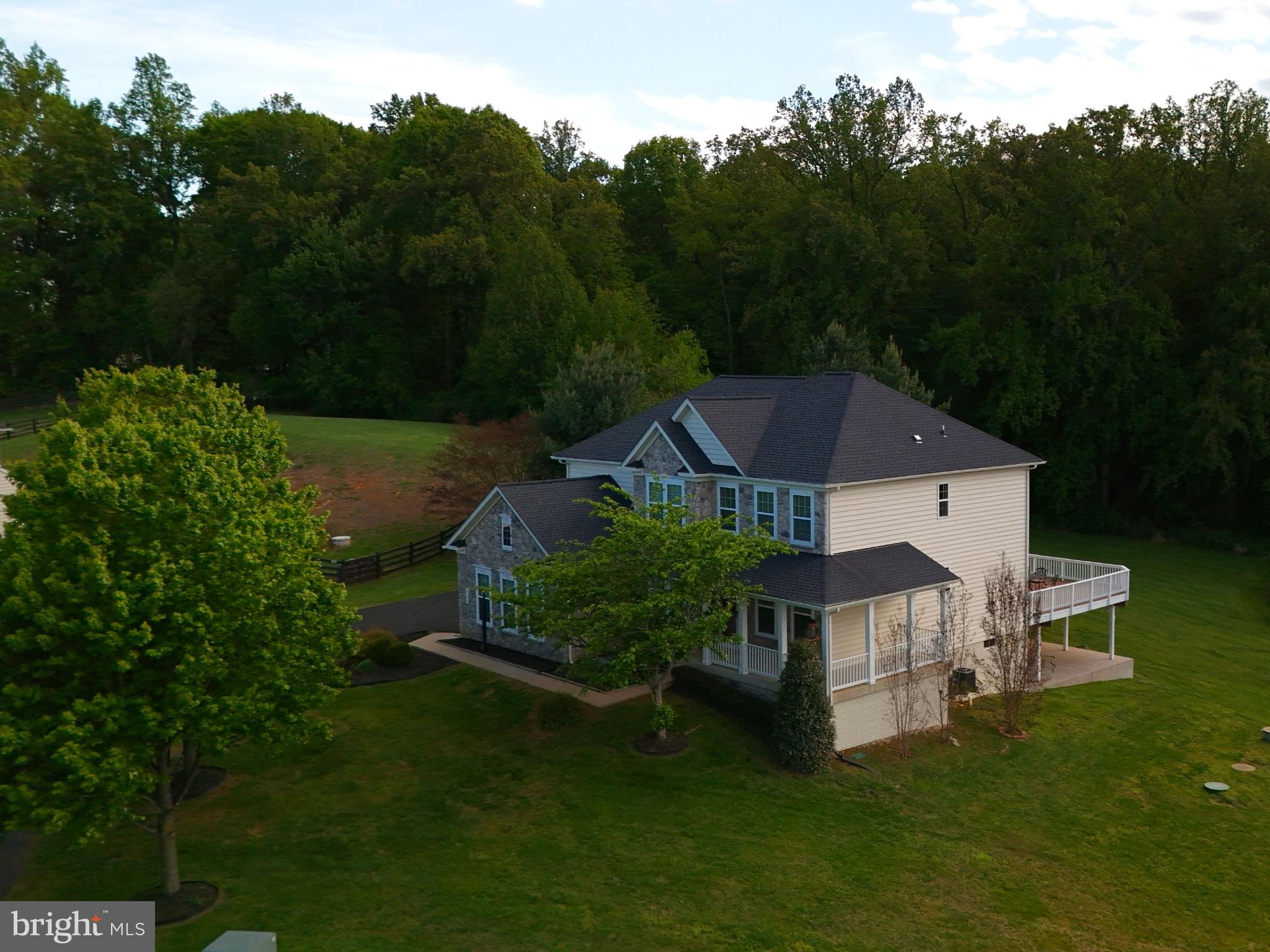 Welcome to your dream home, perched 472 ft above ground level in the prestigious rolling hills of Jamison Farms. This exceptional Colonial offers panoramic views, privacy, and refined living on 1.12 acres—and is being sold partially furnished, inside and out, for a true turnkey opportunity.

The northeast-facing exterior features a Natural Fieldstone Mosaic façade, manicured landscaping, and a charming wraparound front porch along the right wing of the home. Inside, a dramatic 30-ft ceiling grand foyer opens to formal living and dining rooms. The open-concept main living area includes 9ft ceilings throughout, 6-ft-wide natural fieldstone mosaic fireplace, recessed lighting, recessed surround sound speakers, connected to a 75” 4K Samsung TV, all included with the sale.

A library/office with 8-ft French doors houses a massive oak executive desk, ideal for working from home. A nearby half bath adds convenience. The chef’s kitchen features a 5’ x 6.5’ island, granite countertops, stainless steel appliances, walk-in pantry, and butler’s pantry, with a new gas range burner installed Dec 2025. Light floods the XL sunroom with soft window treatments and blackout curtains, offering full backyard views.

Step outside to the 672 sq ft deck (2018), furnished with a cast-iron dining set for entertaining. Lighted steps lead to a private backyard oasis with mature trees, expansive lawn, and sweeping valley views.

The second floor offers four fully furnished bedrooms, all with walk-in closets. The primary suite features a king-size bed, separate sitting area, and a spa-inspired bathroom with soaking tub, double vanity, private toilet room, and dedicated dressing area. The three additional bedrooms each include queen-size beds and matching hardwood armoires made of mahogany and oak. A second-floor laundry adds convenience.

The walk-out basement includes  1,400 sq ft of finished space and 1,556 sq ft unfinished, ideal for a sauna, studio, or hobby area. The finished lower level features a bedroom with egress window, walk-in closet, full bath with real stone tile, carpeted den, and abundant natural light. Exercise equipment is included, and a swing attachment remains.

Additional features/updates:
    •    Charcoal black asphalt shingle roof (2019) w/ 30-yr warranty
    •    Concrete patio w/ ramp & steps (2019)
    •    Whole-home salt-water softener (2022)
    •    New underground sump pump
    •    Exterior septic pump replaced; system serviced 2019
    •    Irrigation system, weatherized; control panel in 2-car garage

Legal Furnishing Clause: All furnishings shown in the property, interior and exterior, are included “as-is, as shown” with the sale of the home. Seller and agent make no guarantees regarding condition, functionality, or assembly of included furnishings.

This home offers luxury, comfort, and turnkey living with breathtaking views—an unparalleled opportunity in Jamison Farms.