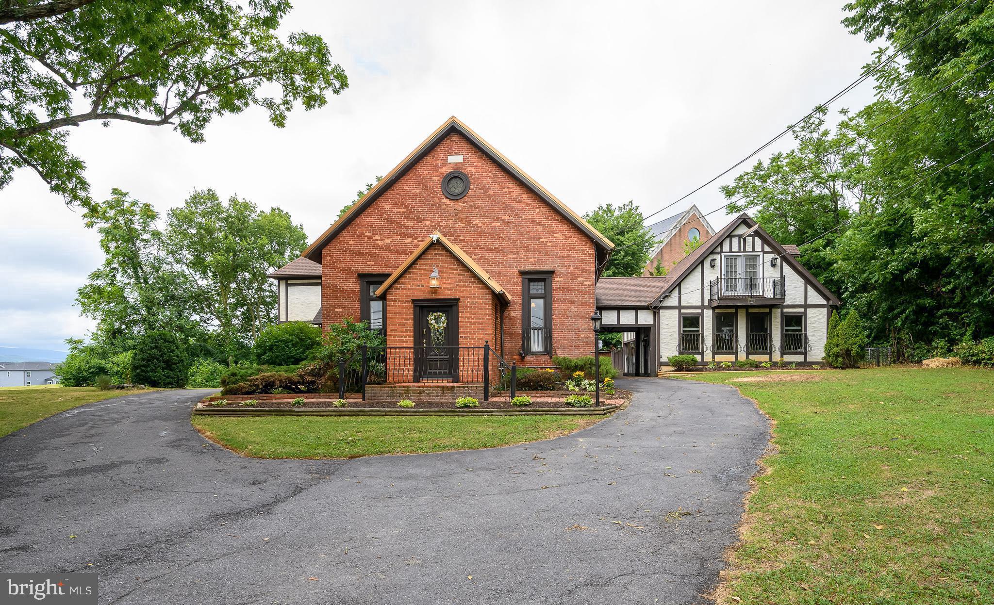 This beautifully preserved former church was thoughtfully transformed into a unique residential retreat, while retaining much of its original architectural character. Built in 1881, this brick property offers plenty of living space and combines historic craftsmanship with comfortable modern living.
The home's soaring interior spaces create an extraordinary sense of openness, highlighted by a huge formal living room area with the fireplace, adding comfort and atmosphere throughout the seasons.  Open formal dining room, adjacent to a large kitchen, blends with original design elements that reflect its ecclesiastical heritage. Home features 2 bedrooms with 2 full bathrooms.  Master bedroom, with a large sitting area and an outside balcony, is complemented by an impressive loft, offering flexible space for a home office, library, or creative studio.
A thoughtfully designed family room with a woodstove includes a second loft with beautiful mountain views.  Cute balconies and large decks with expandable awning are perfect for spending your evenings outside.  Oversized garage with a huge working area for any home project. Additionally, there is a 1 bedroom, 1 bath apartment with the full kitchen above the garage for guests. 
The property sits on 0.5 acre and offers the charm and tranquility of the countryside, while remaining conveniently located near Charles Town's shopping, dining, and commuter routes. 
This home, priced below the appraisal, with newer (2019) metal roof, fenced yard, and a swing, is an opportunity to own a piece of West Virginia history, where architectural heritage and residential comfort come together in a truly one-of-a-kind setting.  A rare piece of history!