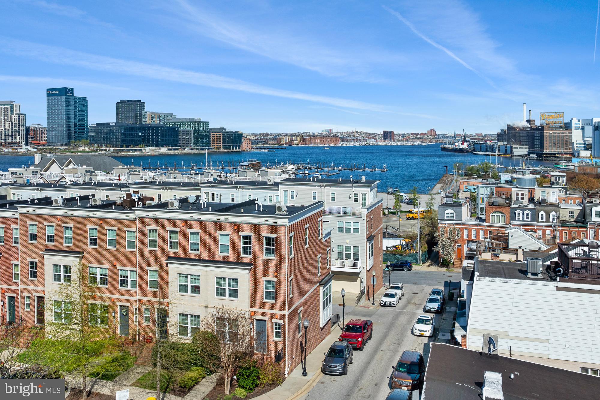 Welcome to high-end city living in this exceptional 4-story end-unit townhome, offering stunning water views and a front-row seat to the iconic Domino Sugar sign. Built in 2016, this luxury residence is packed with premium features and modern upgrades, combining comfort, style, and sophistication in one beautifully designed home.

Step inside to discover an open, light-filled layout with expansive windows, wide plank hardwood floors, and custom finishes throughout. The gourmet kitchen is a showstopper, featuring rich granite countertops, stainless steel appliances, custom cabinetry, and a large island perfect for both everyday living and entertaining. The spacious living room centers around a sleek gas fireplace and opens to a private deck.

The top-floor family room is a true retreat, complete with a full wet bar, a dramatic double-sided gas fireplace, and access to an expansive rooftop deck—perfect for entertaining or simply taking in the city skyline and waterfront scenery. The home features two gas fireplaces and a built-in Sonos sound system throughout, delivering seamless audio in throughout the home.

Generously sized bedrooms are filled with natural light, and the two second floor bathrooms are elegantly appointed with double sinks and modern finishes, creating a clean, luxurious atmosphere.

Additional features include a two-car garage, upgraded lighting, custom closets, and energy-efficient systems. As an end unit, this home offers extra privacy and natural light from windows on three sides—highlighting those gorgeous views from every level.

Located just steps from waterfront promenades, restaurants, parks, and all the best of Baltimore’s vibrant urban lifestyle—this is a rare opportunity to own a luxury townhome with top-tier finishes and breathtaking views.