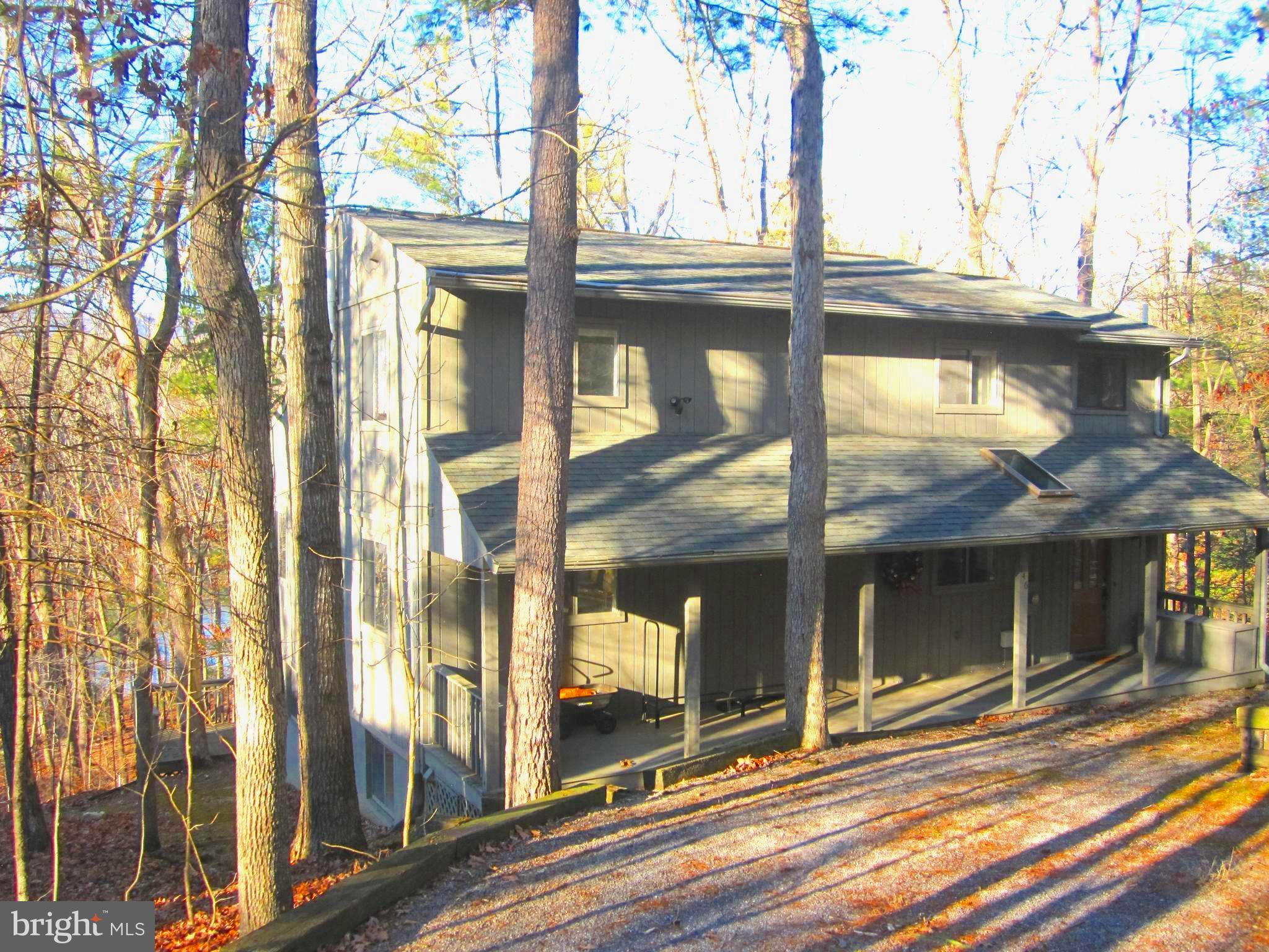 THIS IS A REAL LAKE LAUREL PROPERTY. There are just a few trees in the way of the walk to  the Lake at the bottom of the property. There are two large decks from which the view can be enjoyed. The main floor has a long screened porch and the downstairs has a  fully enclosed and heated  deck.
The home is 2,946 square feet  and has 4 nice sized bedrooms and three full baths. Most floors are real wood. The main floor has a very large  dining/living area, a beautiful stone fireplace and a bed room and  full bath. Upstairs has two bedrooms and a full bath which could be a comfortable primary suite. Downstairs also has a large living room and game area and a bedroom and full bath and laundry room with a washer and dryer.