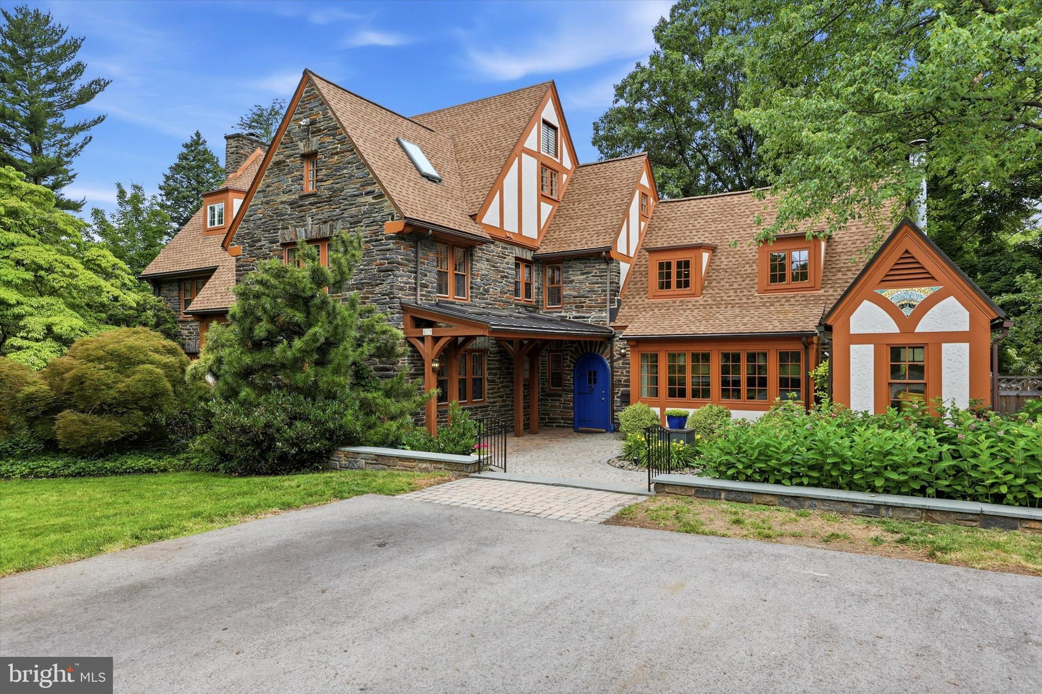 SHOWINGS START SUNDAY
Welcome to this charming 6,000+ sq. ft. stone Tudor 'gingerbread house', bursting with unique architectural character. A welcoming courtyard with a local artist's mosaic-decorated shed leads into a Moravian-tiled entrance hall. Inside, a dramatic, light-filled two-story great room features a gas fireplace and a breathtaking overlook balcony with a structurally reinforced carved balustrade. The large open kitchen is an entertainer’s dream, boasting two-toned cabinetry, Jerusalem stone countertops, a custom tiled backsplash, a built-in family workspace, and a custom wooden banquette with a matching dining set. Double sliding doors lead to a low-maintenance Trex deck and a pristine in-ground pool, which offers total peace of mind with a recently replaced piping system, new tile, new coping, fresh resurfacing, and a convenient outdoor powder room.

Designed for seamless modern living, the main floor also hosts a formal dining room with a stone fireplace, a large family/playroom with built-ins and a second stone fireplace, and a private home office featuring its own dedicated exterior entrance and walkway to the street. Upstairs, the second level features a luxurious primary suite alongside three additional bedrooms—one with a custom built-in captain's bed—and three full bathrooms. The expansive third floor offers incredible flexibility as a guest wing or fitness space, featuring two additional bedrooms, a central sitting room with built-in storage, and a fourth full bathroom. A full-length unfinished basement provides a powder room, utility sink, and massive storage potential. Perfectly situated for great walkability, this storybook home sits just two blocks from Merion Elementary School and an easy stroll to downtown Narberth's shops, dining, and the Center City train.