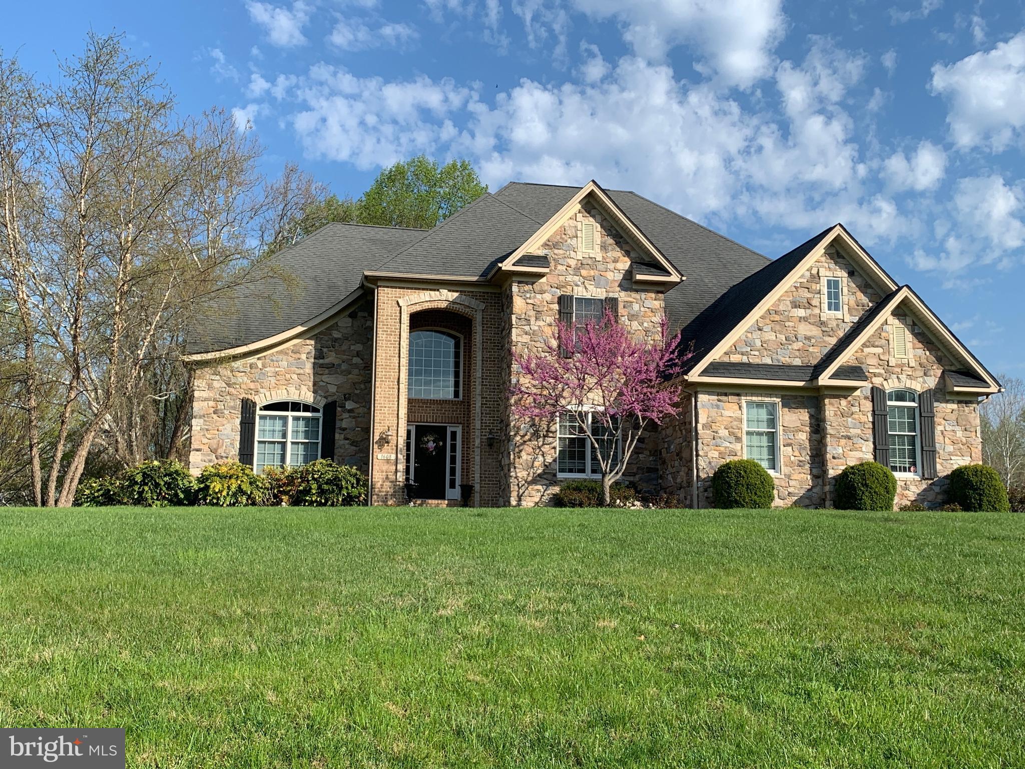 Welcome to 1608 Angleside Road — a stunning custom-built estate tucked away on a quiet no-thru cul-de-sac in Regent’s Ridge, Fallston. Set on a breathtaking 4.11-acre homesite surrounded by privacy and natural beauty, this original-owner residence offers nearly 6,400 finished square feet designed for both luxurious everyday living and unforgettable entertaining.

From the moment you arrive, the home’s timeless stone and brick exterior, manicured landscaping, and stately presence create an unforgettable first impression. Inside, a grand two-story foyer with a sweeping curved staircase sets the tone for the elegance and warmth found throughout the home.
Thoughtfully designed with both comfort and functionality in mind, the main level features a dramatic vaulted living room, elegant formal dining room, private office, convenient rear staircase, and beautifully connected living spaces ideal for modern living. The heart of the home is the expansive open-concept kitchen featuring a large center island, spacious dining area, walk-in pantry, and butler’s pantry — all flowing seamlessly into the inviting family room anchored by a cozy gas fireplace.

Just off the family room, the covered porch creates the perfect extension of the home, offering peaceful views and effortless indoor-outdoor living.

Everyday conveniences have been exceptionally considered, including a spacious laundry room with built-in cabinetry, utility sink, and laundry chute, multiple coat and storage closets, and a walk-in drop-zone closet just inside the oversized 3-car garage entrance.

Throughout the home, rich architectural details including arched doorways, Andersen windows, custom built-ins, and quality craftsmanship add warmth, character, and timeless appeal.

Upstairs, a versatile loft area with custom cabinetry and dual desks creates the perfect homework station, study area, or secondary living space. The luxurious owner’s suite serves as a true private retreat with its own fireplace, his-and-her closets, spacious bathroom with soaking tub and separate shower and a bonus room.   Three additional upper-level bedrooms offer exceptional space and privacy, including a Jack-and-Jill bath arrangement and a private en-suite bedroom ideal for guests or multigenerational living.

The fully finished lower level dramatically expands the home’s living and entertaining possibilities with a sprawling game room, great room, exercise or theater space, full bar area, full bath, and extensive storage. Step outside to the beautifully designed stone patio with built-in fire pit — the perfect backdrop for entertaining friends or enjoying quiet evenings under the stars.

Additional highlights include dual heating systems, abundant storage throughout, an oversized driveway with extensive parking, and construction by award-winning builder Brockton Homes.
Rarely does a property offer this combination of craftsmanship, scale, privacy, warmth, and premier location. This is more than a home — it’s a private retreat designed for the way people truly want to live.

Coming Soon in Regent’s Ridge — this exceptional Fallston property is one you won’t want to miss.  Showings to begin June 12!