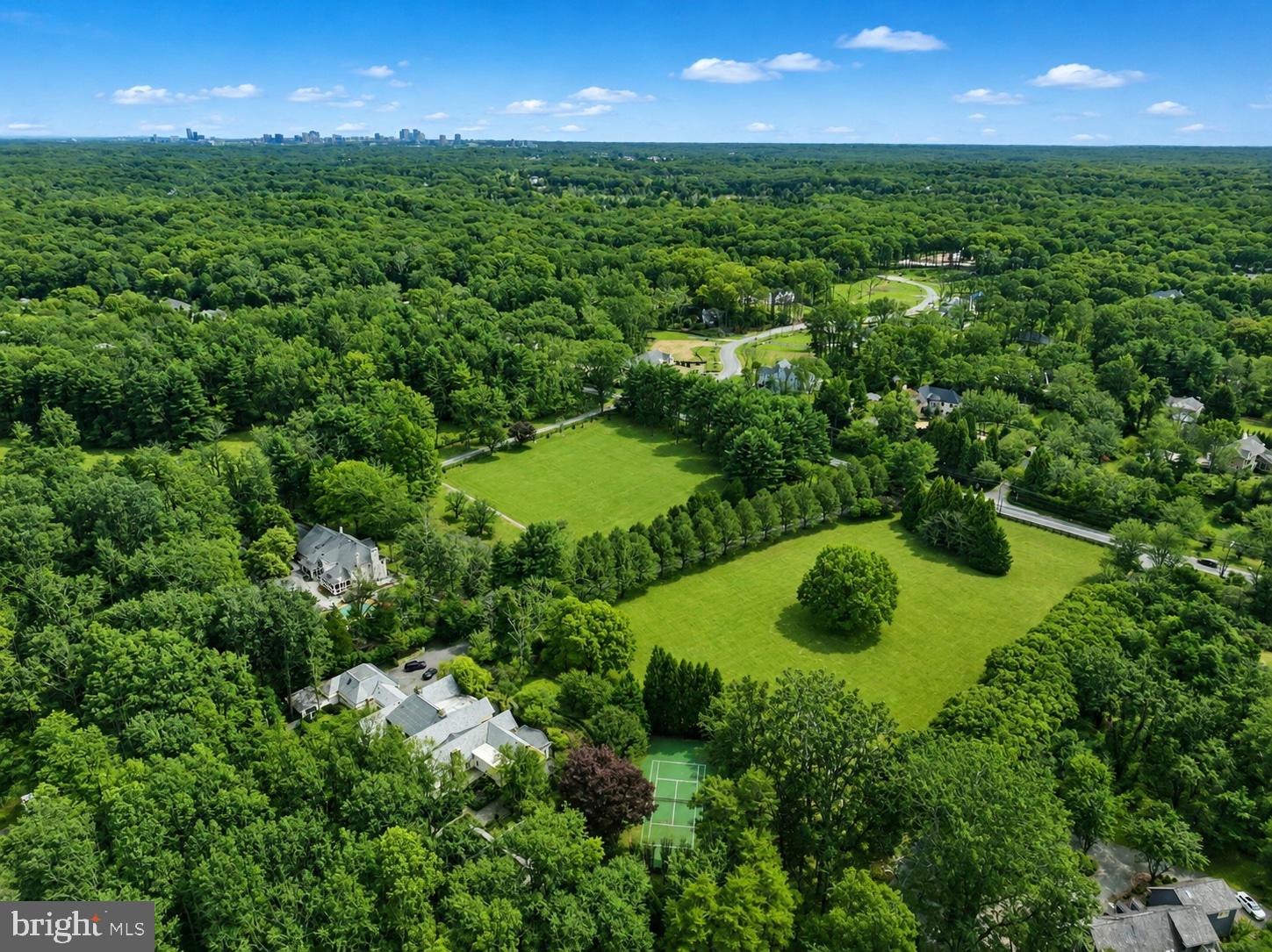 Welcome to Stone Wood Manor—set on a pristine 5+ acres with a gated entrance, tennis court, full gym, tree-lined driveway, and a two-story guest house complete with its own kitchen. A pool can be added. The drive reveals a stately manor surrounded by manicured lawns, cascading fountains, vibrant gardens, and a tranquil pond beside the tennis court. Designed for intimate living and entertaining, the interiors glow with natural light, showcasing intricate millwork and six elegant fireplaces. The gourmet kitchen—anchored by custom cabinetry, chef-caliber appliances, and its own wood-burning hearth—flows into a cheerful breakfast room and a soaring two-story great room framed by walls of glass. The Versailles-inspired grounds, envisioned by landscape artist Charles Owen, are enchanted with stone fountains, French wrought-iron gates, and pea gravel paths. Minutes from Tysons Corner, McLean, and Washington, D.C., Stone Wood offers refined living in a resort-like setting—an oasis of elegance and tranquility.