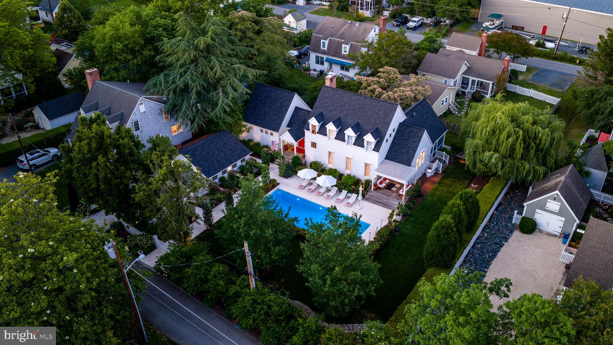 Beyond the white picket fence, a storybook garden unfolds—lush, curated, and unmistakably Oxford. Perfectly positioned just moments from the beach, ferry, and waterfront park, 208 Factory Street offers a rare blend of timeless village charm and sophisticated modern comfort. Thoughtfully enhanced with updated mechanical systems since 2019, this three-bedroom residence has been meticulously maintained and beautifully reimagined for effortless living. Sunlight pours into the airy, open- concept living, dining, and kitchen spaces, where hardwood flooring flows seamlessly throughout and every room feels connected to the outdoors. Designed with exceptional flexibility, the home features two private primary suites—one conveniently located on the main level and a second occupying the upper floor. The upstairs retreat serves as a true sanctuary, complemented by a beautifully renovated spa-inspired bath featuring a glass-enclosed porcelain tile steam shower. The main-level suite offers its own renovated bath and charming loft area, creating an equally inviting private escape. Just off the kitchen, a dedicated office provides the ideal work-from-home setting, while multiple outdoor living spaces invite relaxation and entertaining throughout the seasons. Enjoy quiet mornings on the intimate sitting porch overlooking the pool, gather with friends on the screened porch, or simply savor the beauty of the impeccably landscaped cottage gardens that envelop the property. Completing the offering is a detached one-car garage and an enviable location in the heart of Oxford. A home that captures the very essence of Eastern Shore living—elegant yet approachable, refined yet welcoming, and perfectly connected to one of Maryland’s most treasured waterfront communities. Here, every detail has been thoughtfully curated to create a lifestyle as beautiful as its surroundings. ---{Luxury & Special Features} Electric retractable awnings | Heated floor in second-floor primary bath | Glass-enclosed steam shower with rain shower in second-floor primary bath | Towel warmer in second-floor primary bath | Tesla charger in detached garage | Moen smart water shutoff valve | Water pressure booster pump | Lawn irrigation system | Updated mechanical systems since 2019 | Hardwood flooring throughout | Two primary suites, including a main-level primary | Dedicated office/flex room | Screened porch | Poolside sitting porch | Detached one-car garage | Cottage gardens and white picket fence setting |