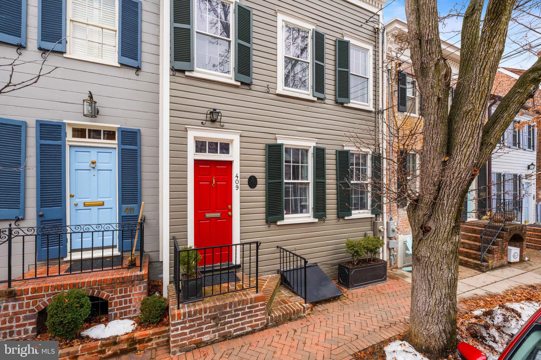 Built around 1905 and set on one of Old Town Alexandria’s most picturesque streets, this exceptional historic residence offers timeless character, thoughtful updates, and an unbeatable location in the heart of this beloved waterfront community. Rich in history, the property is storied to have originally served as a neighborhood store before being transformed into the distinguished residence it is today. A classic façade welcomes you into a formal entry foyer highlighted by an exquisite staircase and a convenient coat closet.  The main level unfolds into a gracious double parlor with two front-facing windows overlooking S. Lee Street. Gorgeous original wood floors extend throughout the first and second levels, complemented by high ceilings and abundant natural light. Anchoring the expansive living space is a beautiful wood-burning fireplace and custom built-in bookcases designed in a distinctive step-back style, creating a warm and inviting focal point. The space flows seamlessly into the formal dining room, ideal for both everyday living and elegant entertaining.  The dining room features high ceilings and custom wallpaper, adding depth and sophistication. The renovated kitchen blends style and function with chic countertops, glass-front cabinetry, high-end appliances, and a large pantry. A charming French door opens to the private rear patio, where a slate terrace shaded by a beautiful magnolia tree creates a serene outdoor retreat with convenient alley access.  Upstairs, the home offers three spacious bedrooms and two beautifully renovated bathrooms. The primary bedroom is a true retreat, featuring a lovely bay window bump-out, custom built-ins, and a walk-in closet with a California Closets system. A skylight in the upper hallway fills the space with natural light.  An unfinished basement provides excellent storage. Meticulously maintained, the home also features updated systems and windows, offering modern comfort while preserving its historic integrity.  This is a truly special offering in the heart of Old Town Alexandria—just moments from shops, restaurants, parks, and the waterfront, with easy access to Washington, DC, and the airport. A rare opportunity to own a remarkable piece of Alexandria’s history in one of its most sought-after locations.