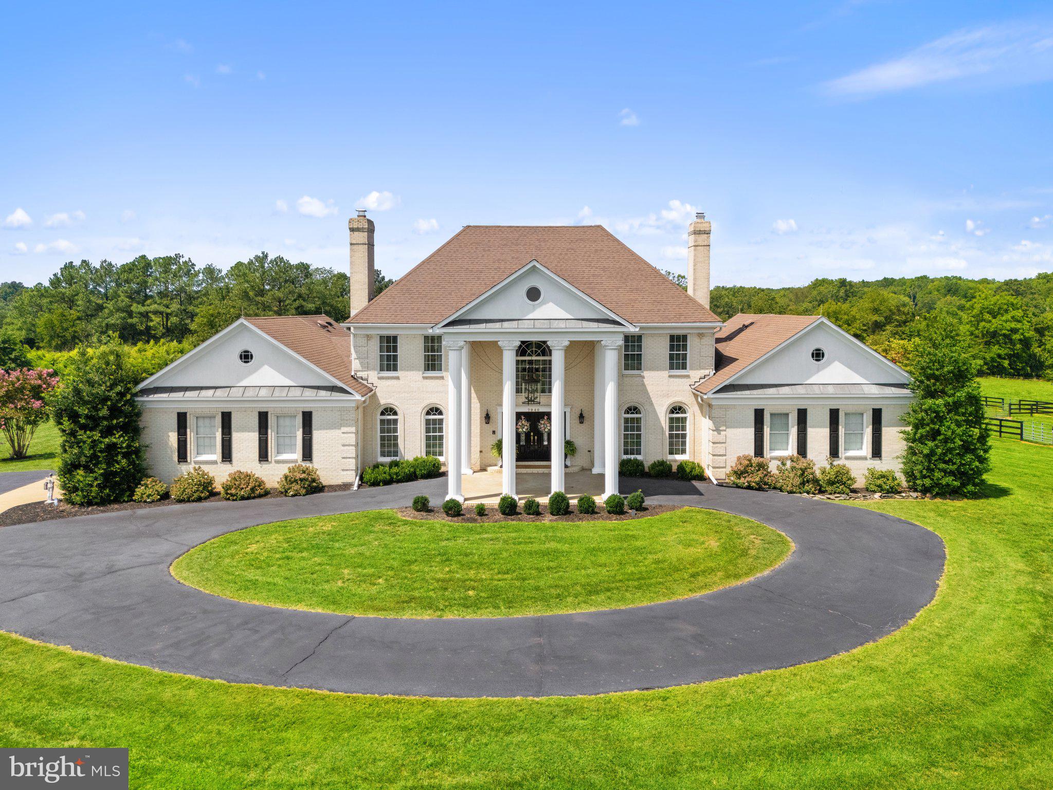 Nestled on 11 scenic acres, this 6,000 sq. ft. estate offers luxury, craftsmanship, and stunning views. A gated entrance and fenced yard provide privacy, while the all-brick design adds charm. Designed for elegance and comfort, the home features wood floors throughout most of the main level, fresh paint (2025), and new carpet (2025). Expansive windows capture rolling pastures, a private vineyard, and peaceful landscapes, making it a true home for heart and hoof.

**All offers are due by Monday at 12pm** The grand foyer, with Carrera marble floors and dual curved staircases, sets the tone for this exquisite residence. At the front of the home, a formal living room and dining room, both with fireplaces, offer an inviting space for gatherings, with the dining room leading to the gourmet kitchen. Custom cabinetry by Warrenton Cabinetry, soft-close hardware, under-cabinet lighting, and an 8.5’ island with a Black Walnut top create a chef’s dream. High-end appliances include a 48” ILVE Nostalgie Series double oven, custom range hood, Miele refrigerator, freezer, wine fridge, and smart coffee system. A stylish brick backsplash with soft gold finishes adds sophistication. Adjacent to the kitchen, the mudroom offers convenient garage access and features custom storage, brick flooring, a laundry sink, and a front-load washer and dryer. The two-story great room showcases a wall of windows, custom built-ins, wet bar, fireplace, and dual French doors leading to the rear deck. A private home office with custom oak bookcases provides an ideal remote workspace.
The main-level primary suite is a luxurious retreat, featuring private deck access and two walk-in closets with custom organizers. The updated en-suite bath includes dual vanities, soaking tub, and a dual-head shower, creating a spa-like atmosphere.

Upstairs, the landing overlooks the great room, enhancing the home’s open feel. A second primary suite includes an updated en-suite bath with soaking tub, dual vanities, and walk-in closet. Two additional bedrooms share a renovated hall bath with modern finishes.

The lower level features a home gym and dry sauna. The rec room is great for movie or game nights and opens to a patio with a built-in outdoor fireplace. An additional room, full bathroom, and large storage area complete the space.

For equestrian and agricultural enthusiasts, the estate includes a 1.5-acre Vidal Blanc vineyard (4 years old), offering the potential for a unique experience. The 4-stall horse barn, with room for additional stalls, features an insulated tack and feed room with washer, a wash stall with hot and cold water, and a large loft for hay and storage. Four paddocks with three-board wood fencing, a designated round pen area, and two expansive fields with automatic waterers make this a true equestrian haven, all surrounded by serene natural beauty. 

A separate 3-bay workshop/garage (30’ x 50’) includes a 400-amp electrical service, a 10’ bay for an RV, boat, or tractor, built-in tool benches, and RV power ports (30amp/50amp), also usable for EV charging. The oversized 2-car attached garage offers additional storage and convenience.

The professionally landscaped grounds feature mature trees, and an expansive deck with a gazebo. A Catalina Luxury Berkshire hot tub (seats six, conveys) adds relaxation. A custom-built, moveable chicken coop completes the property’s rural charm.

This exceptional estate offers timeless elegance, breathtaking views, and outstanding equestrian and vineyard amenities—an opportunity rarely found.
