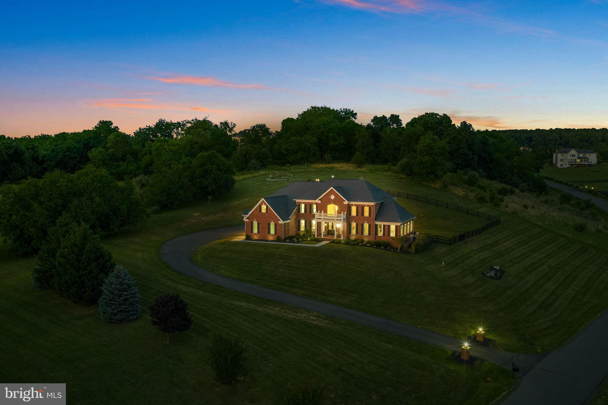 Price improvement on this Gorgeous Estate with Blue Ridge Mountain Views set on 3.06 acres in Western Loudoun County . This exquisitely renovated estate offers nearly 8,300 square feet of luxurious living, thoughtfully designed to capture both natural beauty and architectural presence; offers the rare balance of peaceful countryside living with remarkable everyday convenience. Just minutes from major commuter routes ie. Rt 7, Rt 9, and the Dulles Greenway, the property is approximately 30 minutes from Dulles International Airport and within close proximity to shopping destinations such as Whole Foods, Wegmans, Costco, Target, Trader Joe’s, Leesburg Premium Outlets and more. Residents enjoy easy access to acclaimed wineries, charming floral gardens and flower farms, fine dining, schools, and the historic villages of Waterford and Leesburg.
A grand arrival begins with new double entry doors opening into a dramatic two-story foyer, where a striking double-sided curved staircase creates an unforgettable first impression. From this central vantage point, the home immediately reveals its scale and intentional design. Formal living and dining rooms gracefully flank the foyer, while a sun-drenched conservatory and expansive windows fill the home with natural light throughout the day. At the heart of the home, the gourmet chef’s kitchen is both sophisticated and functional—anchored by an impressive 11-foot island with seating and appointed with a curated suite of Café appliances, including a French-door wall oven, built-in microwave, French-door refrigerator, a custom vented hood, and 36-inch commercial-style gas range. The kitchen also features an expansive Breakfast Room area that easily accommodates a table for 12, as well as a built-in desk area that adds convenience for daily living. Designer lighting and hardware, marble tile and luxurious countertops complete the space, while the adjoining Sunroom and the Breakfast Area overlooks the grounds and opens to a new Trex deck, seamlessly connecting indoor and outdoor living and leading to a beautifully crafted flagstone patio. The main level is completed by a 2-story family room, back stairwell to the upper level, private office, mudroom, and laundry room, plus powder room, thoughtfully designed with elevated finishes to reflect the home’s cohesive sense of luxury.
Upstairs, the primary suite serves as a true private retreat, offering both scale and thoughtful design. The suite features a separate sitting area, a generously sized secondary walk-in closet (approximately 9' x 7') within the bedroom, and an exceptional primary dressing room accessed through the ensuite bath measuring approximately 24 feet by 10 feet—creating a boutique-style wardrobe experience rarely found in residential design. The spa-inspired bath is equally impressive, showcasing a freestanding soaking tub, dual vanities positioned opposite one another, TWO water closets, and a double walk-in shower—delivering a retreat-like experience within the home. Three additional bedrooms and fully renovated ensuite bathrooms continue the home’s elevated design throughout the upper level.
The fully finished lower level, spanning approximately 2,600 square feet, offers exceptional flexibility for multigenerational living and/or entertaining. This level features a second gourmet kitchen with a 10-foot island, expansive living and entertaining areas, a private suite with custom walk-in closet and ensuite bath, two additional bedrooms with shared full bath, storage, media room, and additional flexible spaces. Direct walk-up access provides seamless connection to the backyard. Outdoors, enjoy over 3 acres of peaceful countryside, including a 1-acre fenced yard with a county-approved pool fence and gates, offering both privacy & future potential.
New: Hot Water Heater. 2 HVAC. Well Pump. Double Front Entry Doors. Hardscape. Workshop. Extensive Renovations. Plus more.