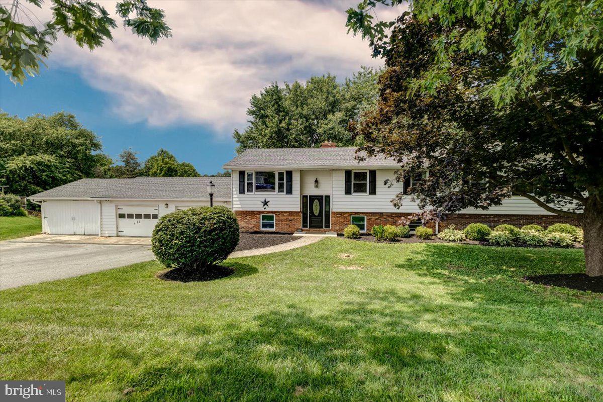 Welcome to this spacious 4 bedroom, 3.5 bath home offering nearly 3,000 square feet of finished living space situated on an incredibly private approximately 3/4 acre lot with beautiful rural views overlooking picturesque farmland. This versatile home is ideal for multigenerational living, featuring two primary suites located on the main level and positioned across from one another for added privacy, each with its own private bathroom. One primary suite also includes an additional sitting room, perfect for a home office, reading area, nursery, or private retreat. The spacious kitchen offers an abundance of cabinetry and opens directly to the large covered rear deck, providing the perfect place to enjoy morning coffee, outdoor dining, or relaxing evenings while overlooking the peaceful backyard. The outdoor space truly sets this property apart with a playground, tree house, chicken coop, large fenced garden, attached storage shed, and an additional rear garage offering flexible space for storage, hobbies, equipment, workshop needs, or potential vehicle storage. The attractive exterior features a partial brick front, beautifully curved paver walkway, and an oversized attached garage with an incredible amount of space for vehicles, workshop areas, equipment, and more. Inside, you will find hardwood floors, luxury vinyl plank, ceramic tile, vinyl, and laminate flooring along with updated light fixtures and ceiling fans throughout. The lower level offers a cozy woodstove and an incredibly unique hidden room that can be transformed into a private bar area, movie theater, game room, hobby space, home office, or your own personal retreat. Recent updates include a heating and cooling system installed in 2020, architectural shingle roof, gutters, downspouts, and below grade drainage replaced in 2019, stainless steel Wi Fi capable washer and dryer replaced in 2023, new well pump switch in 2025, water filtration system, and two electrical panels. Laundry convenience is enhanced with a lower level laundry area plus additional hookups in the main level hall bathroom for a stackable washer and dryer. Located in a peaceful country setting while remaining commuter friendly to Sykesville, Westminster, Howard County, Frederick County, Montgomery County, and DC. Enjoy nearby recreation at Morgan Run Park, Piney Run Park, the Carroll County Ag Center, and the Farm Museum. This exceptional property offers privacy, flexibility, incredible outdoor amenities, and a lifestyle that is truly hard to find.  Some photos may include virtual staging.