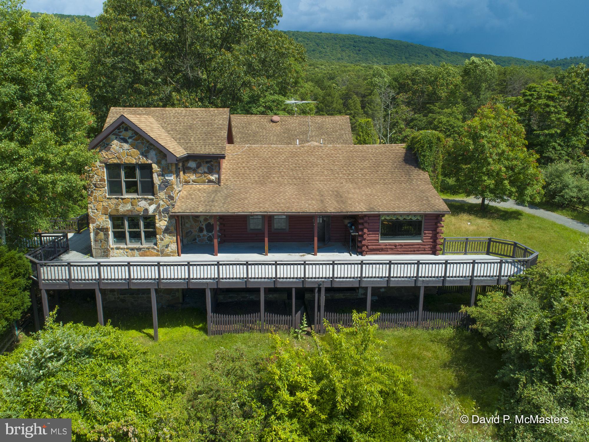 EXTRAORDINARY  5100 sf CUSTOM  LOG/STONE  CABIN ON 18+- ACRES. Exemplary craftsmanship.  A work of art.   Beautiful views. Beautiful Sunsets from the decks.  Private 4BR 4BA  LOCATED ABOUT 5 MILES FROM HISTORIC  BERKELEY SPRINGS WHICH HAS BEEN NAMED ONE THE BEST ARTS TOWNS IN THE COUNTRY. HUGE WRAP AROUND   TREX DECKS AND COVERED PORCHES, VAULTED, CATHEDRAL  LOG CEILINGS AND WALLS,   Wood floors,  Library/ offices with lots of built in book shelves and more. LOTS OF WINDOWS.  NICE Spacious  KITCHEN. BUILT-IN BARBECUE ON DECK. 13 MOSTLY OVERSIZED ROOMS TO CONJURE WITH. PLEASE CLICK ON THE DOCUMENTS TO SEE FULL FLOOR PLANS AND ROOM SIZES.  SEE ALSO  2 detached 2 CAR GARAGES w/  work shops, storage, electric. EXTERIOR WOOD STORAGE .  HAS SAUNA IN 2'd Primary bedroom suite  IN BIG MOSTLY FINISHED BASEMENT.  Lots of work/storage room.  EXCELLENT PRIVACY AND WILDLIFE GALORE!  Great for entertaining.  Bring the family and friends. Hunting allowed. 
THIS UNRESTRICTED PROPERTY WOULD MAKE A GREAT PRIMARY HOME OR A RETREAT/VACATION HOME   THERE ARE MULTIPLE OVERSIZED ROOMS. Great lay out for entertaining. ROOM YOU WILL NEED FOR HOSTING FRIENDS AND FAMILY. WILL LIKELY SPEND LOTS OF TIME ON THE HUGE WRAP AROUND DECKS AND RETREAT TO THE VERY LARGE COVERED  Screened porch patio OFF THE KITCHEN IN THE COLDER MONTHS.  Sits deeply on the property off a paved driveway.  2 satellite dishes Connections for 12 TVS
THIS HOME WOULD ALSO MAKE A GREAT RETREAT CENTER. OR Air B&B. (THE SWIMMING POOL AND THE POOL Building  HAVE NOT BEEN USED FOR SEVERAL YEARS AND WILL NEED WORK DONE TO THEM). The Deck has substructure support for hot tub; wiring and heating in place.