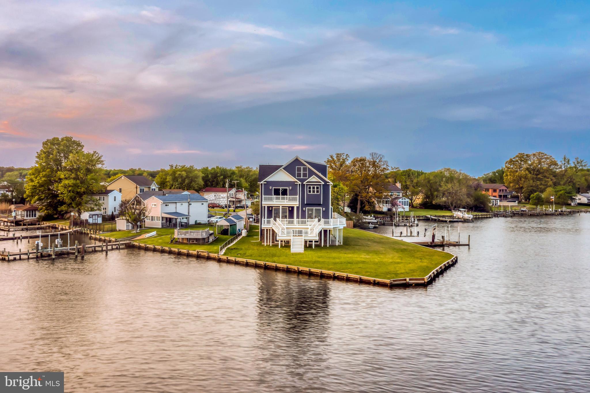 Welcome to 7801 Deboy Avenue. This new construction craftsman beach style smart home sits on a private point on Bear Creek with water views from every single oversized window. This brand new home features over 5,400 square feet of living space with 5 bedrooms, 4 full bathroom, and an extremely rare vantage point of 386 ft of waterfront. Enter through the 4 car garage and travel the grand oak staircase or take the private-4-stop elevator to the next 3 levels. The builder was purposeful in his planning for the property as he widened the entire foot print an additional 5 feet to give a true landing to the elevator step out and to make each bedroom that much bigger. The main level’s open design includes a massive kitchen with 2 elongated islands, black stainless smart appliances, a full bathroom, a bedroom/office and a stone-smart fireplace. All of the appliances were carefully chosen and positioned for efficiency and convenience including the gas stove top that was imported from Italy. Walk out onto over 1,600 square feet of composite decking overlooking the unobstructed and vast views of Bear Creek. The next level showcases 2 additional bedrooms, a full bath, as well as a magnificent owner's suite. The owners suite has a private walk-out balcony overlooking the water and an exquisite owner's bathroom with a standing glass shower, a jetted soaking tub, and two private vanities. This level also includes an extra large laundry room with smart washer and dryer. Again, you can see water from every single room in this home through the custom oversized windows; even in the laundry room. The peak level features a sprawling 27 by 18ft recreation room. Greet guests at the front door using the smart home technology from several locations throughout the home. If this is not enough, walk out to the private pier to enjoy a weekend on the water complete with 2 boat lifts and a jet ski lift. Other features include a tankless water heater, dual zoned HVAC, three quarter inch oak flooring throughout, a smart gated entry, and custom trim and paint package throughout. Don't miss this rare opportunity to immerse in luxurious and serene water front living.