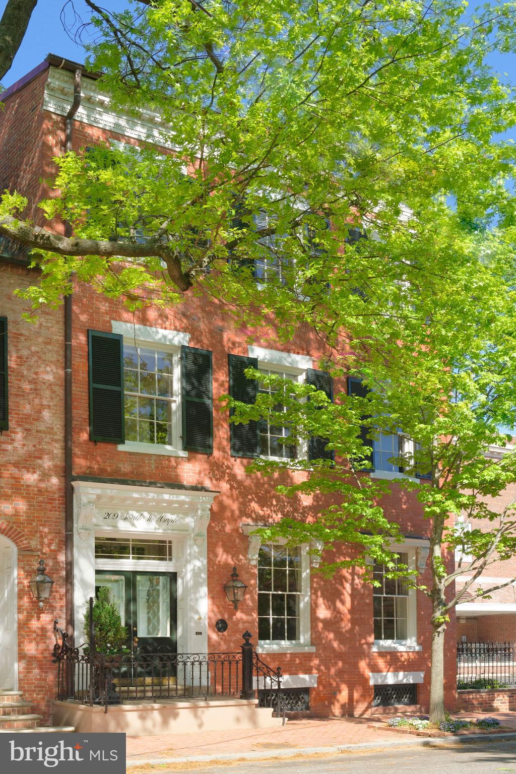 Stunning 1835 Flemish bond brick home is an architectural masterpiece, showcasing an exceptional level of craftsmanship and an unparalleled sense of history. From the moment you see the elegant exterior, you're transported to a bygone era, captivated by the meticulous restoration work that has preserved its timeless charm. Step inside and you'll be greeted by a wealth of original features - the gleaming heart of pine floors, ornate plaster moldings, soaring 12’-foot ceilings, and a grand double parlor that exudes refined sophistication. The towering windows flood the interior with natural light, while eight fireplaces with original mantels throughout the home lend a cozy, inviting ambiance. The stately dining room, enriched by a coffered ceiling, crystal chandelier and fireplace, offers an ideal setting for hosting dinner parties for friends and family. A beautifully appointed powder room sits across from the bar area to accommodate guests.  The culinary enthusiast will delight in the renovated chef's kitchen complete with top-of-the-line appliances, chic coffee bar, hardwood floors, and an exceptional island with additional seating. The kitchen flows seamlessly into the family room framed by floor-to-ceiling windows and French doors that open to a delightful patio and garden offering an idyllic setting for outdoor entertaining and alfresco dining. Upstairs, four spacious bedrooms and three baths provide ample room for comfortable family living and the second-floor library provides a tranquil retreat for reading and relaxing.  The primary suite exudes sophistication and comfort featuring a fireplace, dressing room with custom wardrobes, walk-in closet, and a luxurious marble bath. Two off-street parking spaces and a small garage offering convenient access and storage complete this historic gem.