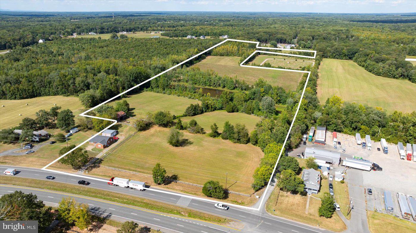 A truly rare 31.1-acre land offering in Stafford County comprised of four separate parcels, creating exceptional flexibility for a private estate, working farm, family compound, or potential future division. With dual road frontage on both Warrenton Road (Route 17) and Truslow Road, this property offers visibility, access, and long-term opportunity that is increasingly difficult to find. The rolling landscape features approximately 18 acres of cleared and previously hayed fields, extensive open pasture, and fencing already in place, making it ideal for horses, livestock, or agricultural use. This was long ago a beautiful, working horse farm. A picturesque one-acre pond (great fishing here!) anchors the property, complemented by abundant wildlife and mature natural buffers. Existing infrastructure includes multiple barns (four-stall and two-stall configurations with paddock), as well as a 30x25 metal building suitable for equipment storage, workshop, or garage use. With four parcels included, the layout lends itself to multi-generational living, future homesites, or builder exploration (subject to county approvals). The property is improved by a three-bedroom, 1.5-bath brick residence set off the road, with nice square footage and updated main-level finishes. Ideally positioned just minutes from Hartwood, Route 17 conveniences, I-95, and Downtown Fredericksburg, this offering combines scale, infrastructure, dual-road frontage, and location, a powerful combination rarely available in today’s market. A true land opportunity with immediate usability and long-term upside.