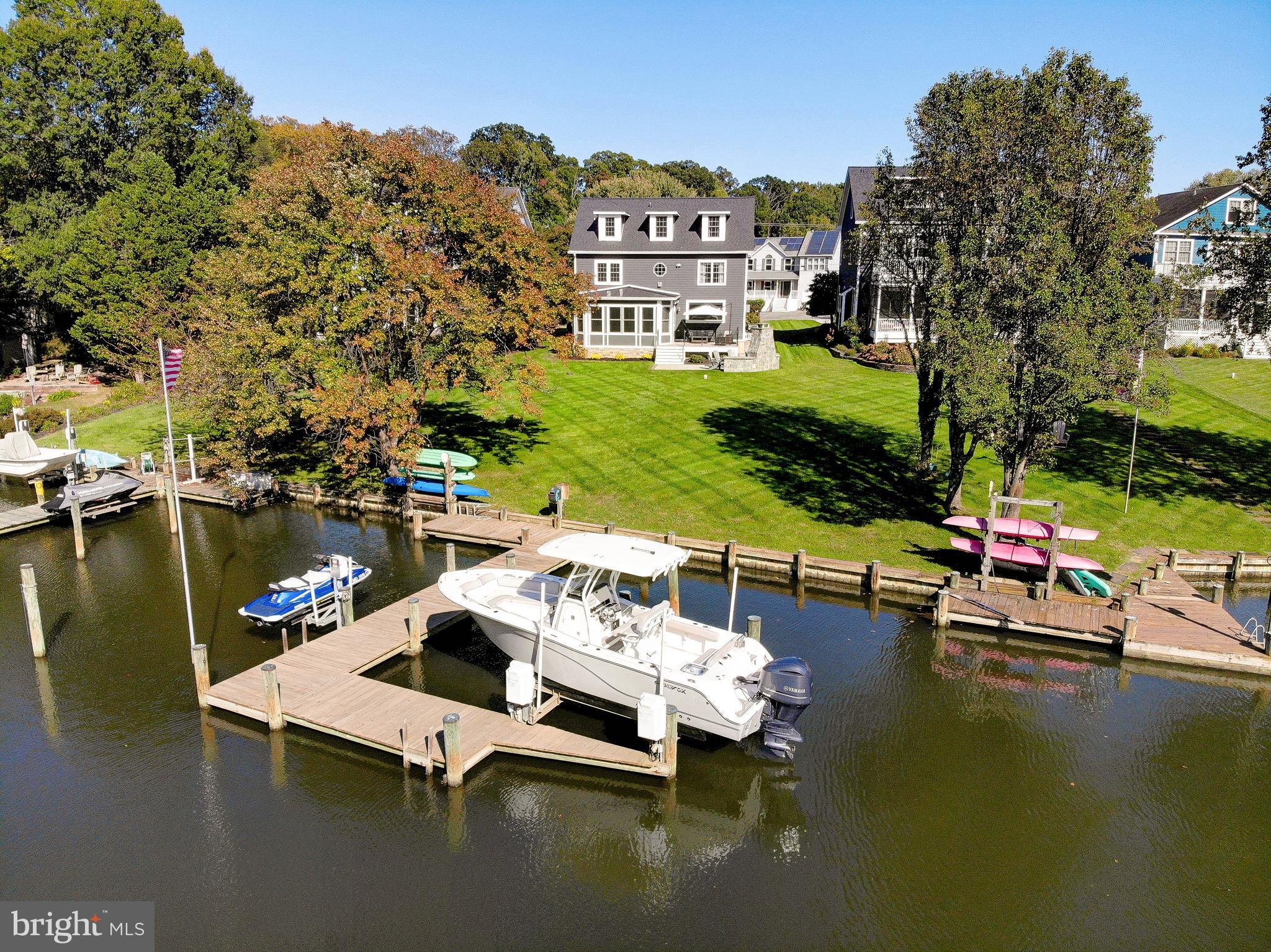 Experience refined waterfront living in this completely reimagined home located in the coveted Loch Haven community, perfectly positioned on the protected waters of Pocahontas Creek with approximately 4 feet of mean low water and just seconds from the South River. This exceptional property offers the ideal blend of serene privacy, premier boating access, and sophisticated design. The home has been meticulously renovated from top to bottom and showcases an expansive open-concept layout designed to maximize both water views and natural light. In addition to the stunning cosmetic transformation, the home features major recent improvements including a brand-new roof, two new HVAC systems, and a newer water heater, offering true peace of mind. At the heart of the home is a stunning gourmet kitchen featuring a large statement island, Thermador stainless steel appliances, quartz countertops, custom tile backsplash, and a picture window perfectly framing the waterfront scenery. The kitchen flows seamlessly into the family room, highlighted by a  linear fireplace with shiplap surround and custom mantel, and continues into the sun-drenched dining area wrapped in walls of windows. The main level also offers a thoughtfully designed mudroom with built-in lockers, a laundry room, a stylish powder room, and a generously sized private office. Throughout the home, you’ll find luxury wide-plank flooring, reinforcing the home’s cohesive, high-end aesthetic. The primary suite is a true waterfront retreat, offering water views, a sitting area, a private fireplace, and a spa-inspired bath with a freestanding soaking tub, oversized walk-in shower, and double vanity. Two additional spacious bedrooms and a beautifully updated full bath complete the second level.
The third floor provides incredible flexibility with a fourth bedroom featuring water views, an additional flex space or fifth bedroom/office, and a newly remodeled full bath—ideal for guests or multi-generational living.
The lower level offers a recreation room, gym, full bathroom, ample storage, and utility space—perfect for both everyday living and entertaining. Outdoor living is nothing short of spectacular. The dining area opens to a deck with glass railings that flows down to a waterside patio with a dramatic stone fireplace, creating a resort-like setting for entertaining or relaxing by the water. The professionally maintained grounds are supported by the irrigation system, and the private pier features a 10,000 lb boat lift and kayak storage, making this a true boater’s dream. With a flat, usable waterfront lot, protected deep water, and luxurious upgrades throughout, this is a rare opportunity to own a turn-key waterfront home in one of the area’s most desirable communities. The Loch Haven community offers an exceptional waterfront lifestyle with a private sandy beach, community marina with boat ramp, playground (tot lot), basketball and tennis courts, and scenic walking trails. Residents also enjoy a vibrant calendar of family and adult social events, creating a true sense of community and an unbeatable place to live, relax, and connect.