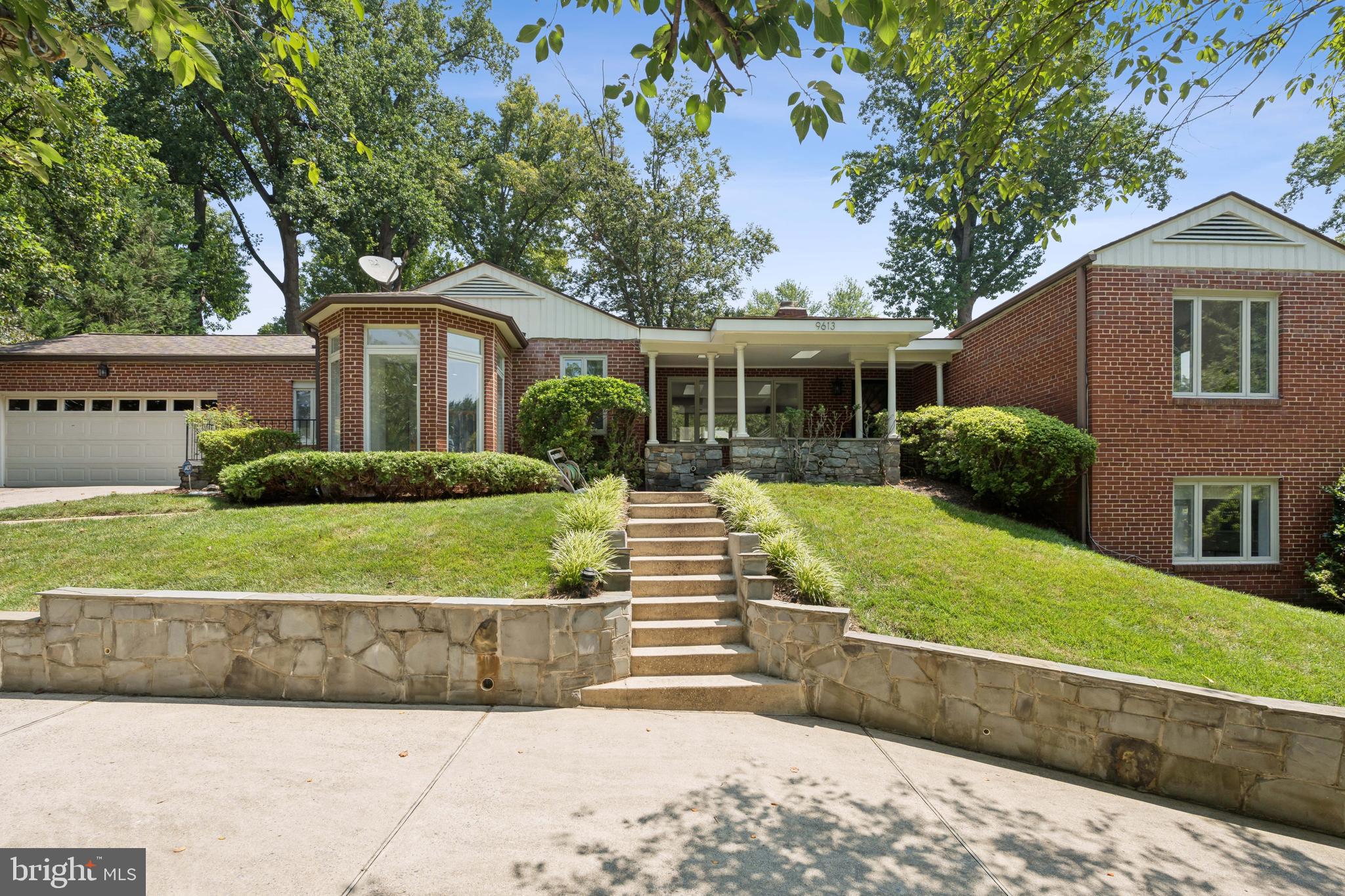 Welcome to 9613 Barroll Lane, an exceptional residence in the heart of South Kensington’s highly coveted Rock Creek Hills. This beautifully updated 4-bedroom+ den, 3.5-bathroom home offers over 4,400 square feet of elegant and functional living space on a private, landscaped 0.41-acre lot—just steps from Rock Creek Park.
Thoughtfully designed for both everyday comfort and entertaining, the main level features a renovated gourmet kitchen that opens to a sun-filled great room with vaulted ceilings and skylights. A formal living room with a wood-burning fireplace and large picture window provides cozy charm and scenic backyard views. The spacious primary suite includes a walk-in closet, ensuite bath, private patio, and a dedicated staircase to the lower level. Two additional bedrooms and a shared full bath, plus a powder room, complete the main level—one bedroom includes French doors leading to a private balcony.
The fully finished, walk-out lower level is perfect for multi-generational living or guest quarters, offering a second full kitchen, large family room with fireplace, fourth bedroom, private den, full bath, and two separate staircases for easy access. Additional highlights include a mudroom off the attached two-car garage, dedicated laundry room, and ample storage throughout.
Step outside to enjoy the professionally landscaped yard with a heated mineral system pool with diving board, water feature and attached hot tub—an ideal setting for summer gatherings and outdoor living.
Located in the desirable Rock Creek Hills neighborhood, this home offers peaceful, tree-lined streets, top-rated public and private schools, and easy access to downtown Bethesda, Washington, D.C., NIH, and major commuter routes. Experience timeless architecture, community charm, and a prime location that perfectly balances nature and city convenience.