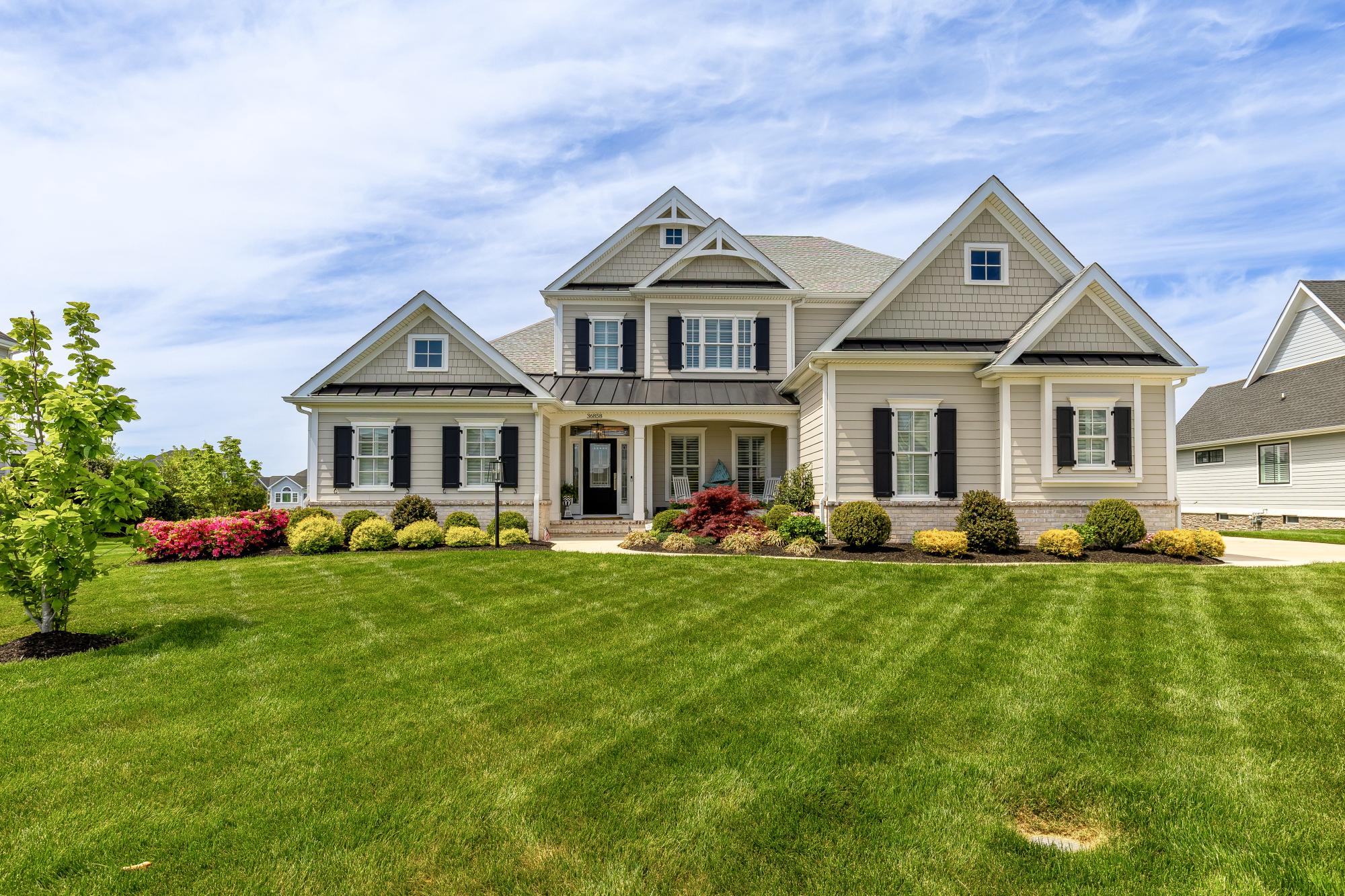 Attention to detail is extraordinary in this stunning coastal-style residence built by Oak Construction, one of Delaware’s most respected custom home builders. Built in 2021, this exquisite home offers a seamless blend of luxury and comfort with 5 spacious bedrooms and 4.5 beautifully appointed bathrooms.
Step inside to an inviting open floor plan featuring crown moldings, recessed lighting, thoughtfully designed living spaces, and beautiful 7" plank engineered hardwood floors throughout the main living areas. The gourmet kitchen is a chef’s dream, showcasing Thermador stainless steel appliances, including a 48" cooktop with double ovens and grill, microwave drawer, and built-in side-by-side column refrigerator and freezer. The oversized 6' x 9' island offers seating for seven and is complemented by Calabria quartz countertops and inset cabinetry, creating the perfect space for everyday living and entertaining.
The family room, anchored by a gas fireplace with custom built-ins, enhances both warmth and character. Stacking glass doors extend the living space into a three-season room, offering effortless indoor/outdoor living.
Retreat to the luxurious owner’s suite featuring two walk-in closets/dressing rooms with a linen closet and professionally designed closet systems. The spa-inspired primary bathroom showcases marble 8" hexagon floor tile with radiant heated floors, a large marble-tiled shower with a corner seat, marble countertops, and a stunning tiled accent wall extending from the vanity to the ceiling behind the mirrors.
Additional bedrooms offer ample space and comfort throughout, and all closets throughout the home feature professionally designed closet systems.
The recently finished lower level provides exceptional flexibility for recreation and entertaining, featuring a spacious game room, dedicated fitness room, and a full bathroom with marble tile flooring and a marble-tiled shower. Exterior access adds additional convenience and functionality.
Outside, enjoy adjoining open space with serene pond views. Relax on the expansive hardscape patio or take advantage of the community amenities, including a pool and fitness center. Professionally landscaped grounds include underground irrigation.
With an attached side-entry garage and ample driveway parking, this home is designed for convenience and elegance. Experience the exclusive lifestyle this remarkable property offers, where luxury meets comfort in every detail.