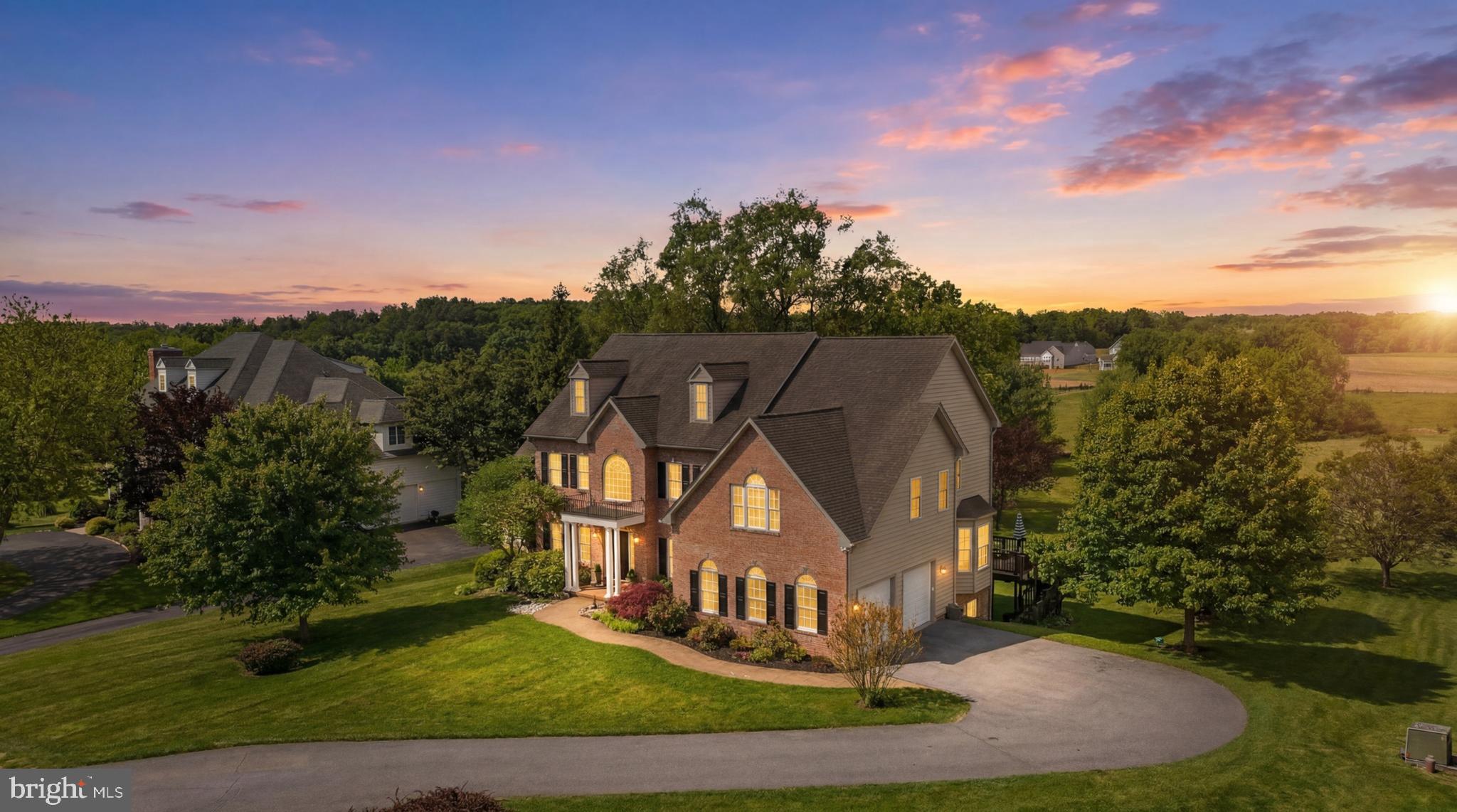 Welcome to one of Cattail Creek’s most extraordinary estate offerings—a timeless brick-front colonial gracefully positioned on a premium 1.21-acre homesite overlooking tranquil pond views and some of the most breathtaking sunsets Howard County has to offer. Framed by stately white pillars, striking black shutters, a grand portico adorned with a designer chandelier, manicured landscaping, rose gardens, an expansive driveway, and dual entertainment decks, this remarkable residence delivers a lifestyle rarely available in today’s market—all without the burden of an HOA. Beyond the impressive façade, a dramatic two-story foyer unfolds with exquisite crown molding, chair rail detailing, shadowbox accents, and rich red oak hardwood flooring. Elegant formal living and dining rooms are adorned with custom millwork, designer lighting, Palladian windows, and refined architectural details, while a stunning conservatory showcases soaring cathedral ceilings, dual chandeliers, custom Italian marble flooring, walls of windows, and direct access to a private deck overlooking the estate grounds. The heart of the home is a spectacular chef’s kitchen designed for both entertaining and everyday living, featuring granite countertops, custom cabinetry, a massive center island with prep sink and dishwasher, commercial-grade stainless steel appliances, six-burner cooktop, exterior-vented professional hood, warming drawer, breakfast bar, window seating, coffee station, and seamless access to outdoor living spaces. Anchoring the main level is a breathtaking two-story family room highlighted by soaring ceilings, dramatic Palladian windows, Restoration Hardware chandelier, extensive custom moldings, and panoramic views of the backyard and pond. A handsome executive study with custom built-ins, spacious mudroom, laundry room, and powder room complete the main level. Upstairs, retreat to an owner’s sanctuary unlike any other, entered through grand double doors and featuring cathedral ceilings, a spacious sitting room, custom wet bar with beverage refrigerator, designer chandelier, and three customized walk-in closets including a California Closet dressing room complete with chandelier. The luxurious spa-inspired bath offers granite vanities, Jacuzzi soaking tub, oversized shower, and private water closet. Three additional generously sized bedrooms and two full baths complete the upper level. Ascend further to the spectacular fourth-level loft retreat with cathedral ceilings, abundant natural light, full bath, and endless flexibility as a guest suite, au pair quarters, fitness studio, executive office, or future in-law suite. The fully finished walkout lower level is equally impressive, offering a kitchenette with maple cabinetry, expansive recreation spaces, two additional bedrooms, a full bath, extensive storage, custom built-ins, and a large utility room equipped with a comprehensive water conditioning, filtration, and softening system. Additional enhancements include new carpeting, fresh designer paint throughout, custom silk and linen draperies, upgraded designer lighting with dimmable chandeliers, landscape lighting, freshly painted decks, EV charging station, solar panels installed in 2022 delivering exceptional energy efficiency with remarkably low utility costs, and a cedar playground. Ideally located just moments from the prestigious Cattail Creek Country Club, residents enjoy convenient access to championship golf, tennis, pickleball, fitness facilities, resort-style swimming, fine dining, social events, and scenic lakes with fountains throughout the community. Zoned to Howard County’s award-winning Blue Ribbon schools, this exceptional estate seamlessly combines luxury, privacy, craftsmanship, and lifestyle into one unforgettable offering.