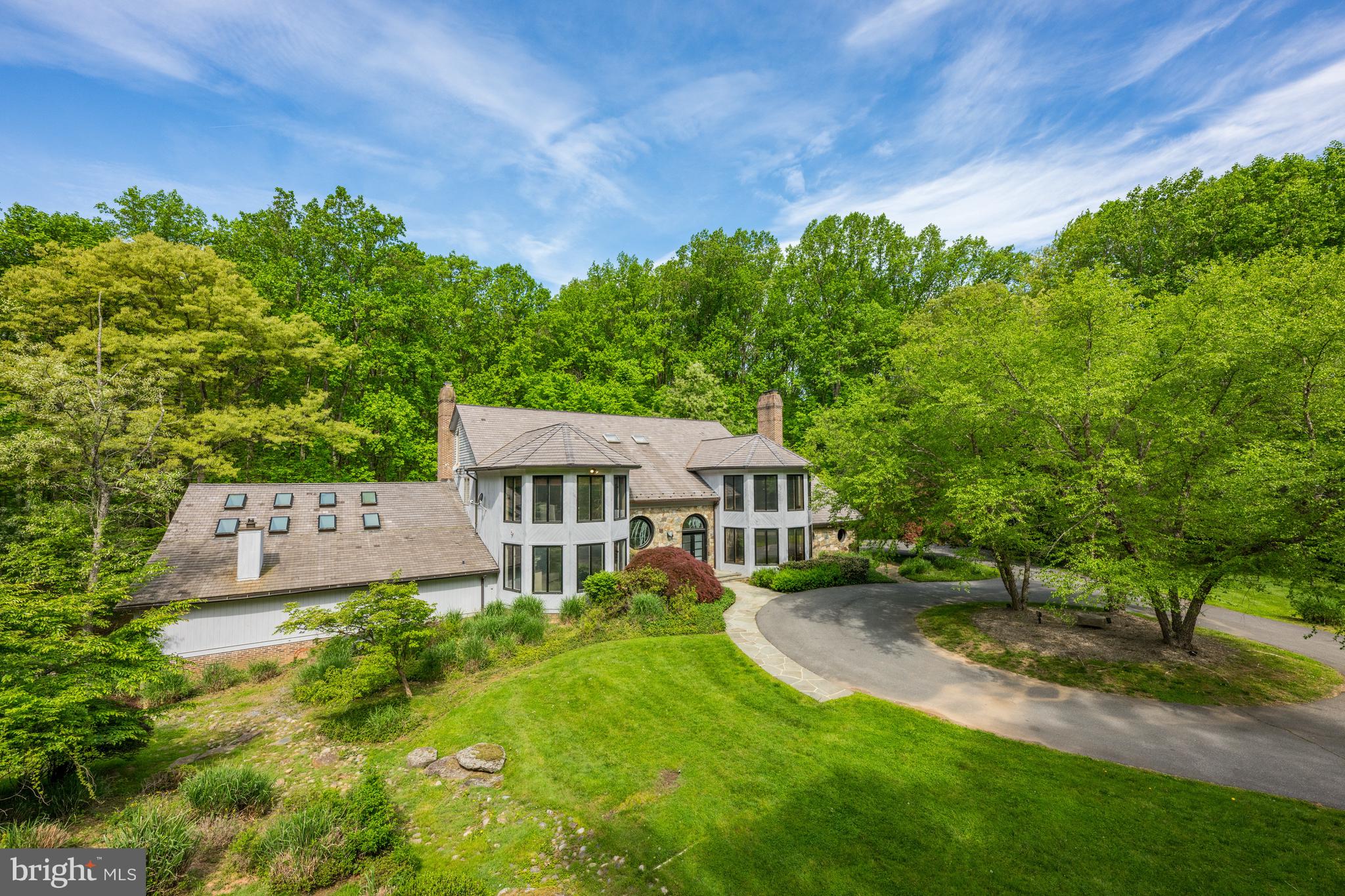 California comes to Potomac! Sited on a beautiful, private 5.68 acre wooded lot, this property is only minutes from the heart of Potomac Village. Everything about this contemporary home is special, inside and out! This designer's own home features a contemporary design with large open spaces. Outdoors you can enjoy a tennis court and multi-level deck with picturesque views. The recently updated indoor Pool, with vaulted ceiling, skylights, separate sauna, and full bath as well as walls of sliding glass doors to the patio and multi-level deck are sure to please. The dramatic, two-story Foyer with balcony overlook is highlighted by a frosted-glass, double-door entry, and circular window with stained glass. The inviting Library also has a two-story vaulted ceiling, balcony overlook, floor-to-ceiling bookcases, and lots of windows. The Living Room can also be used formal Dining Room) and adjacent Family Room with its dry stack fireplace are perfect for large-scale entertaining. The Kitchen is a chef's dream with professional appliances such as a Traulsen refrigerator-freezer, Viking range, and Bosch dishwasher. The center island makes an ideal work space along with a myriad of cabinets. It opens to the informal dining room, which could also serve as a perfect spot for informal meetings. The adjacent Caterer's Kitchen and wet bar make entertaining easy and fun. The upper level is currently configured for two very spacious bedroom suites but can be converted into a total of four bedrooms. The marvelous Primary Suite has a Bedroom with a vaulted ceiling, ensuite Bath, and great views of the outside. There is also a large room perfect for home office with built-ins and big screen tv or an additional bedroom. The adjacent Dressing Room offers plenty of closet space. A second Dressing Room could also be converted into a bedroom and has an ensuite Bath. Lots of options! Speaking of possibilities, the lower level has plenty as well! There is a recreation room with fireplace and sliding glass door to the outside as well as additional space for a future exercise room and a home theater. Two bedrooms and an additional bathroom complete this level. This extraordinary home has seven garages, all of which have been upgraded with speckled flooring. Lots of extra parking space can be found in the turn-around driveway in the front of the house and even more parking space by the lower level garages. garages. The proud new owners can enjoy all that our Nation's Capital has to offer as well as the restaurants, shopping, and entertainment choices in Bethesda and northern Virginia. Both 1-270 and 1-495, as well as three major area airports, are easily accessible. Make this your home for a lifetime!