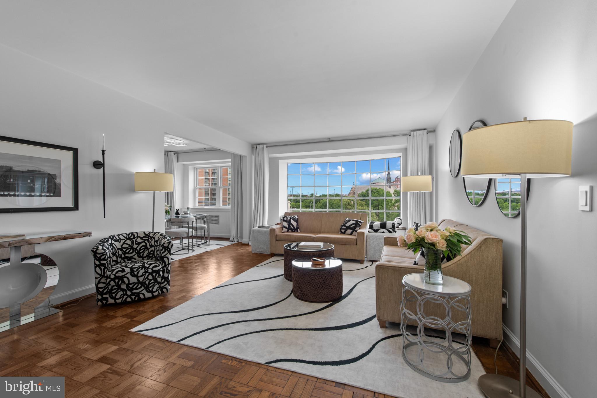 Welcome Home to this inviting contemporary two bedroom condo. Transformed during a comprehensive interior designer-led remodel completed in August ‘25, this cohesive living space features high-end finishes, custom millwork, upgraded systems, and thoughtfully integrated design elements throughout. Located within the Oakenshawe neighborhood, The Carrollton building overlooks the Guilford Gateway Park. The bay-windowed Great Room and sun-lit Dining Room offer panoramic leafy vistas. A custom focal-point feature wall anchors the Great Room, which includes a 68" linear gas fireplace, built-in 76" smart television, and floating display shelves with integrated uplighting. Custom architectural details include expanded openings between the Great Room, Dining Room and Kitchen, improving the flow and sightlines. The designer accent wall and modern statement ceiling fixture create an elegant dining space. Renovated from top-to-bottom, the kitchen offers sleek functionality. The open-concept design includes European-style high-gloss laminate cabinetry, soaring from floor to ceiling with with soft-close drawers and lift-up cabinet doors. Quartz countertops and full-height quartz backsplashes glow with under-cabinet lighting. Large-format porcelain tile flooring spans the room. Upgraded stainless steel appliances include a French-door refrigerator, cooktop/oven combination, built-in microwave, dishwasher, and high-end sink and faucet. Hidden features like the integrated water filtration system, concealed coffee bar with frosted glass interior door and dimmable ceiling fixture round out this chef’s kitchen. A custom-painted mid-century modern inspired black-and-white striped feature wall leads down the bedroom corridor, illuminated by designer ceiling lights. The fully renovated hall bath includes large-format porcelain tile flooring, a floating three-drawer vanity with a  44" trough-style vessel sink, dual spot-resistant brushed nickel faucets, built-in backlit mirrored medicine cabinet with storage compartments, and a tiled backsplash. The large walk-in shower has floor-to-ceiling tile, an integrated shower seat, rain-style overhead showerhead and handheld shower wand, surrounded by a frameless clear glass enclosure. Brushed silver bath accessories, recessed lighting and one-piece dual-flush toilet with soft-close seat complete this spa oasis. The primary bedroom suite has a custom accent wall and multiple closets with an updated sliding door that adds function to the space. A smartly redesigned half bathroom is connected to this bedroom, with finishes that mirror the design and function of the full bathroom. The equally spacious secondary bedroom has an accent wall and custom 88" closet with mirrored French doors. Large windows in both bedrooms and the full bath provide plenty of natural light and sweeping views. The scope and quality of these improvements exceed typical cosmetic updates and represent a substantial investment in both functionality and aesthetics. A sophisticated monochromatic palette unifies the walls, ceilings, doors, trim, and baseboards. Stainless steel door hardware is used throughout the home. Floor-to-ceiling blackout curtains and window treatments are installed over new vinyl replacement windows. Updated electrical outlets and contemporary rocker switches are powered by an upgraded electrical panel. A deeded parking space and storage locker are located within the building. The secure lobby is staffed around the clock, allowing easy management of package delivery and guests. Enjoy luxurious urban living with walkability to Johns Hopkins University, The Baltimore Museum of Art, Sherwood Gardens, Union Memorial Hospital and all the shops and restaurants in Charles Village. Access transportation hubs like Penn Station (2 miles) and BWI Airport (16 miles) within minutes, while Baltimore’s famed waterfront promenade with Harbor East, Harbor Point, Fell’s Point, Canton and Federal Hill are just a short hop