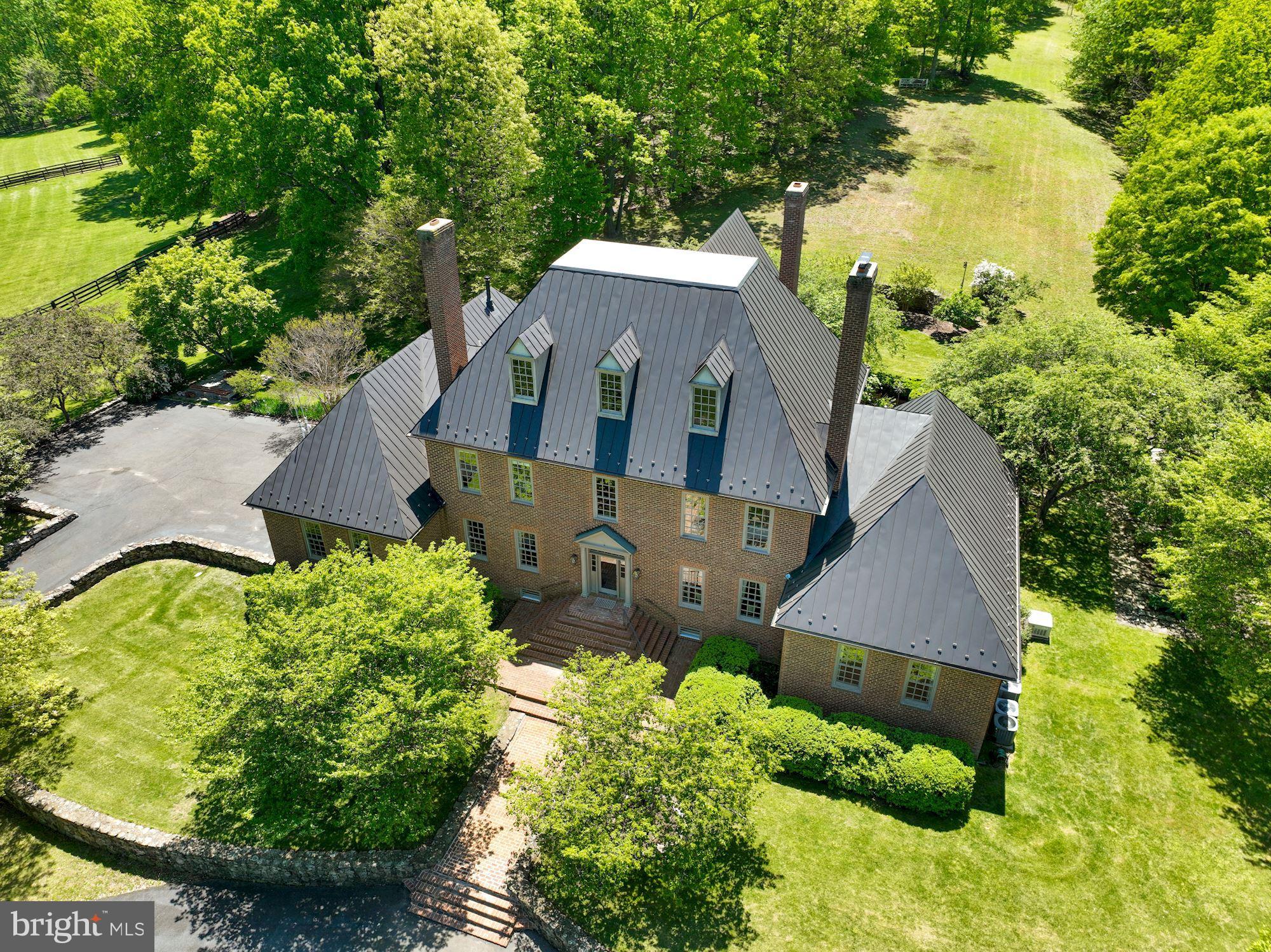Welcome! This stunning brick colonial sits on 50+ gorgeous acres in prestigious Greystone. Throughout this charming 5 Bedroom, 4 Bath custom-built colonial, you'll find pristine craftsmanship & detailing in every room. This 7500+/- sq ft boasts high ceilings, gleaming wood floors, a bright sunroom, and a main level primary suite with its own sitting room and back patio access. Outside, amongst the sprawling acreage, come take in the mountain views, fenced pastures, lush woodlands, Virginia's rolling hills & a private pond. A fully renovated barn (2018/2019) provides a workshop and entertaining space above.