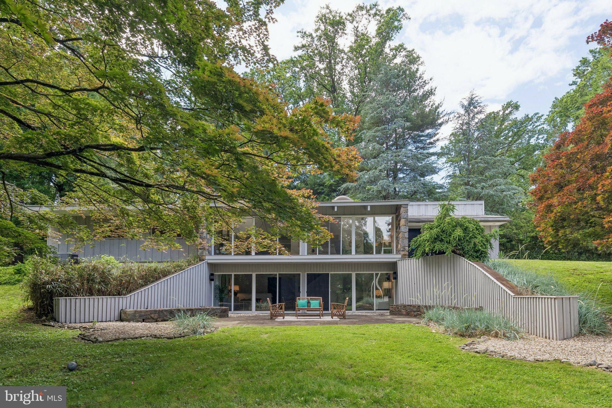 Set at the cul-de-sac end of highly sought-after Monk Road, this custom-designed Mid-Century Modern residence offers striking architecture, exceptional privacy, and tranquil wooded surroundings. Backing to a scenic glen and enveloped by mature trees, the property enjoys peaceful views and a rare sense of seclusion from its elevated position.
The home showcases the clean lines, dramatic scale, and seamless indoor-outdoor connection characteristic of Mid-Century design. Soaring ceiling heights define the main living spaces, while expansive walls of glass fill the interior with natural light and frame views of the surrounding landscape. Freshly painted throughout, the home offers bright, sun-filled interiors with a warm and inviting atmosphere.
A raked Japanese-inspired rock garden with scattered succulents and native plantings further enhances the property's serene setting, complementing the surrounding landscape and architectural character.
Offering four bedrooms and two and one-half baths, the home has been thoughtfully maintained over the years. The spacious family room features a built-in wet bar and opens directly to a private terrace, creating an ideal space for entertaining or quiet relaxation. Abundant closet space throughout, along with a large storage room for garden tools and seasonal items, provides exceptional functionality.
Additional highlights include a fenced yard, carport parking, whole house fan, central air conditioning, oil heat, fresh landscaping, and a newly refreshed interior.
Architecturally distinctive and exceptionally well sited, this is a rare opportunity to own a custom Mid-Century Modern home in one of the area's most coveted locations.
