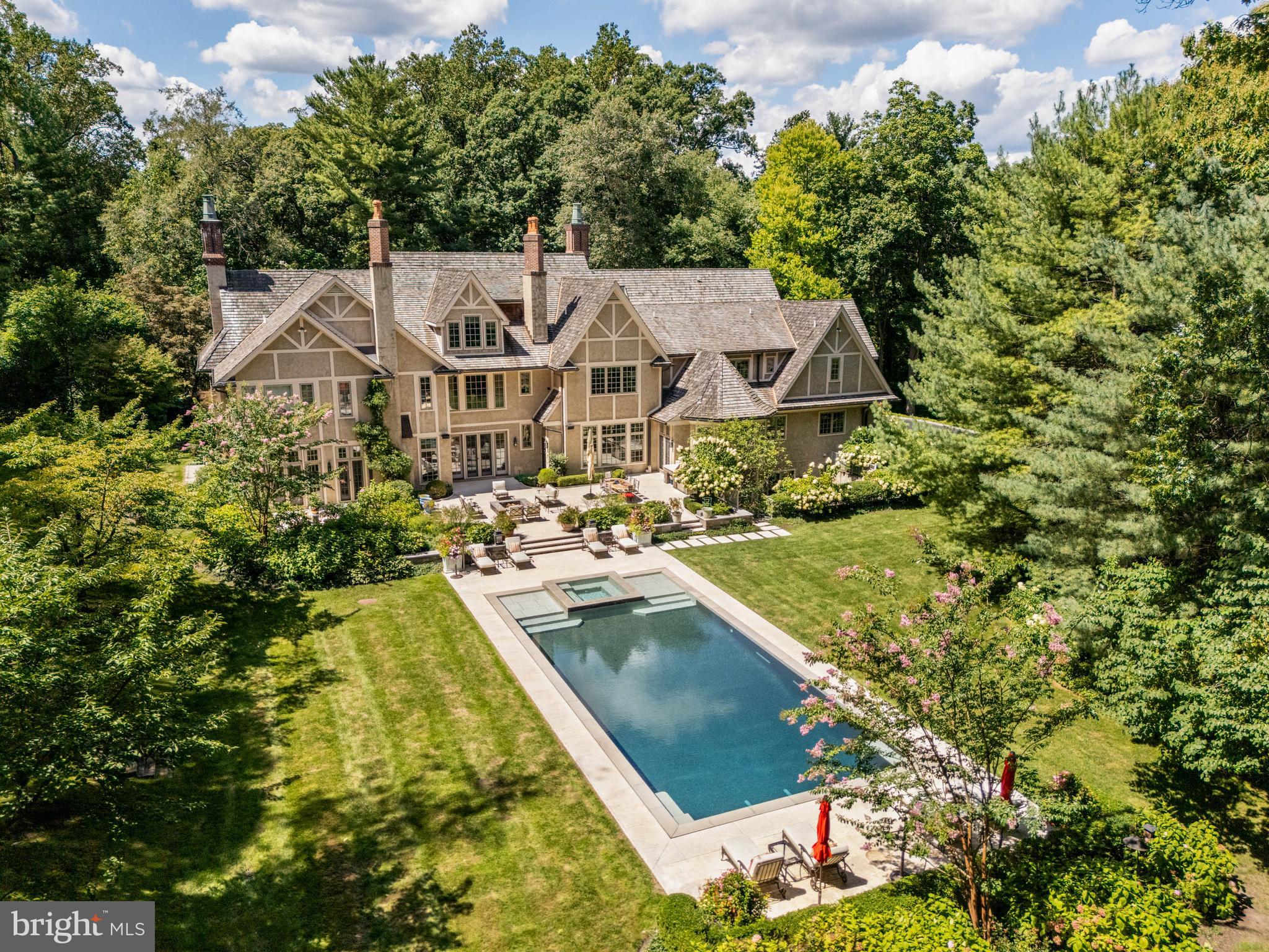 Surrounded by a perimeter of mature forest including evergreens and accessed through a formal gate, Arbor Aves is a Stone Manor estate positioned on one of Northside Haverford’s most coveted and quiet lanes. The front façade combines extraordinary stone and brickwork in a composition of enduring elegance, while the rear elevation, accented with board and batten details, is breathtaking in its symmetry and scale. Framed by gardens and hardscaping designed by Chuck Hess, the light-stone terraces, resort-quality vanishing-edge pool with perimeter overflow, spa, fire-pit, and a fully equipped outdoor kitchen with stainless steel grill create a setting where everyday living feels like a retreat.

 A front-to-rear center hall with inlaid stone floors, and a sitting nook sets a tone of refinement the moment you enter. The living room combines architectural balance with warmth, featuring a fireplace, abundant natural light from 2 exposures, and a charming front window nook that invites reading, conversation, or quiet reflection. The dining room is enriched with ceiling moldings, a cushioned window seat, and ornamental fireplace, while the library offers finely crafted millwork and the solarium glows with wrap-around windows and honed slate flooring. Throughout the main living areas, hardwood floors of white oak—aligned with today’s design preferences—underscore the home’s sophisticated yet timeless palette. Five fireplaces are placed across the home’s 4 finished levels, blending architectural beauty with comfort.

 At the heart of the residence, the Clive Christian kitchen is a showpiece of honey-toned cabinetry, polished Calacatta Gold marble, and professional La Cornue range, anchored by an island with seating for 4. The adjoining breakfast room, crowned by a soaring 12-foot ceiling, overlooks the gardens and flows to the family room, where a fireplace and custom shelving invite gathering. Thoughtful design touches abound: a walk-in pantry with Thermadore wine storage and direct inside access to the garage simplifies unloading groceries, while a “command center” with built-in desk, cabinetry, and shelving provides a practical hub for household management. Crestron automation makes listening to music or controlling lighting and HVAC a breeze.

 The primary suite is a retreat of extraordinary scale and comfort, complete with a private sitting room and fireplace, a beverage center, dishwasher, 2 fully customized walk-in closets, and dual spa-like onyx baths with soaking tub, slab counters, and shared double-sided shower. A 2nd-floor landing introduces another architectural moment—a cozy sitting nook with custom shelving and a window overlooking the front courtyard, creating a quiet retreat above the main foyer. Five additional en-suite bedrooms complete the family level, while the 3rd floor provides flexible space or an in-law suite with living room, generous bedroom suite with full bath, walk in closet, cedar closet, and additional storage.

 The finished lower level is designed for recreation and entertaining, with a professional gym, state-of-the-art theater, walk-in wine cellar, and full wet bar with large island for entertaining, full size dishwasher, refrigeration and cabinetry. Two full bathrooms serve this level: one positioned as a dedicated poolside cabana with changing area and direct access to the gardens, the other adjacent to the exercise room. Every space has been crafted with the same level of finish found throughout the home. An elevator serves all 4 levels.

 Green features—cedar shake roof, Pella Architectural Series windows, blown-in insulation, Energy Star HVAC, permeable pavers, and water-saving fixtures—demonstrate the home’s thoughtful design and efficiency.

 Arbor Aves is more than a residence; it is an experience. Morning light fills the whole rear expanse, spend mornings or afternoons around the infinity pool or in the theater, and evenings draw family, friends to the terraces,