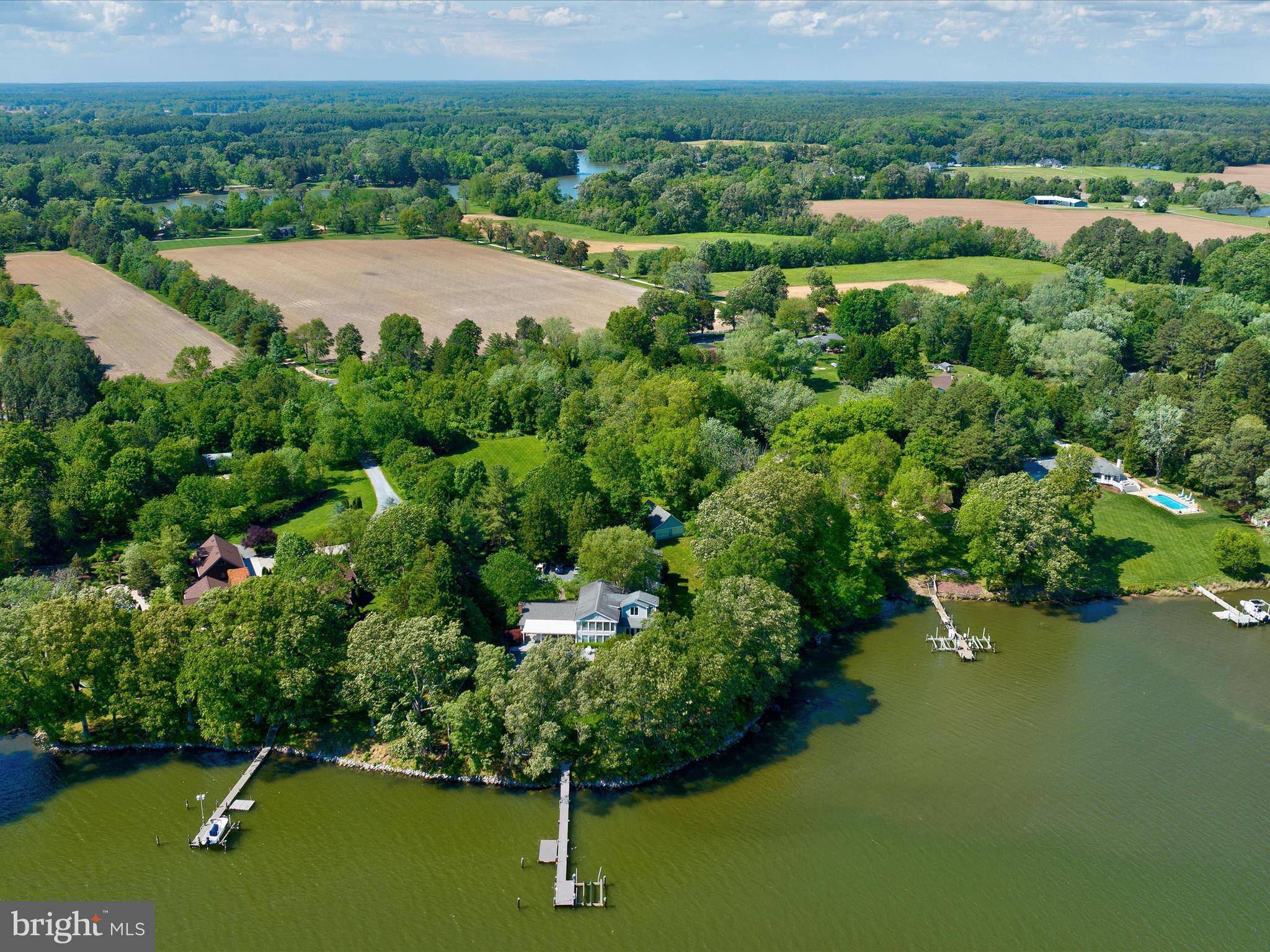 This stunning 5-bedroom, 5.5-bath coastal retreat is set on over 5 acres along the serene shores of Glebe Creek. A shared, tree-lined driveway leads to a beautifully landscaped yard featuring paver walkways, a detached two-car garage with guest quarters above—conveniently connected to the main house by a covered walkway—and a separate cottage with full bath and an attached workshop, offering flexible space for a home gym, office, or art studio.

The main house welcomes you with a charming covered front porch and continues to impress inside with a spacious great room showcasing a vaulted, shiplapped ceiling, custom built-ins, and a cozy wood-burning fireplace.  The kitchen features a butcher-block island with seating, a cozy breakfast nook, and seamless flow into the dining room and sunroom. The sunroom, bathed in natural light, opens directly to the pool area, creating an effortless indoor-outdoor living experience.  The main-level primary suite is a true sanctuary, featuring a tray ceiling, wood-burning fireplace, and French doors opening to a private waterview deck. The luxurious primary bath offers a vaulted ceiling, dual-sink vanity, a classic clawfoot tub, and a separate walk-in shower, creating a spa-like retreat within your own home.  The main level also includes a den with an attached full bath, a laundry room, a powder room, and a mudroom for everyday convenience.

Upstairs, you'll find four additional bedrooms and three full baths, including two en-suite bedrooms—one of which features its own private sunroom. The remaining two bedrooms share a well-appointed hall bath, offering comfort and convenience for family and guests alike.

Outside, enjoy a riprapped shoreline, a private dock equipped with a boat lift, a floating dock, and water and electric—plus approximately 5 feet of mean low water depth, perfect for boating enthusiasts. Relax on the slate patio beneath a pergola with fans, or take a dip in the infinity-edge pool, which is heated for year-round enjoyment.

Easton, Maryland, known as the New Hamptons of the Chesapeake Bay by Forbes Magazine, is conveniently located 1.5 hours from D.C. and Baltimore, and 2 hours from Philadelphia. Just minutes from fine dining, shopping, healthcare, theatres, galleries, museums, golf courses, a country club, a yacht club, and a jet airport.
